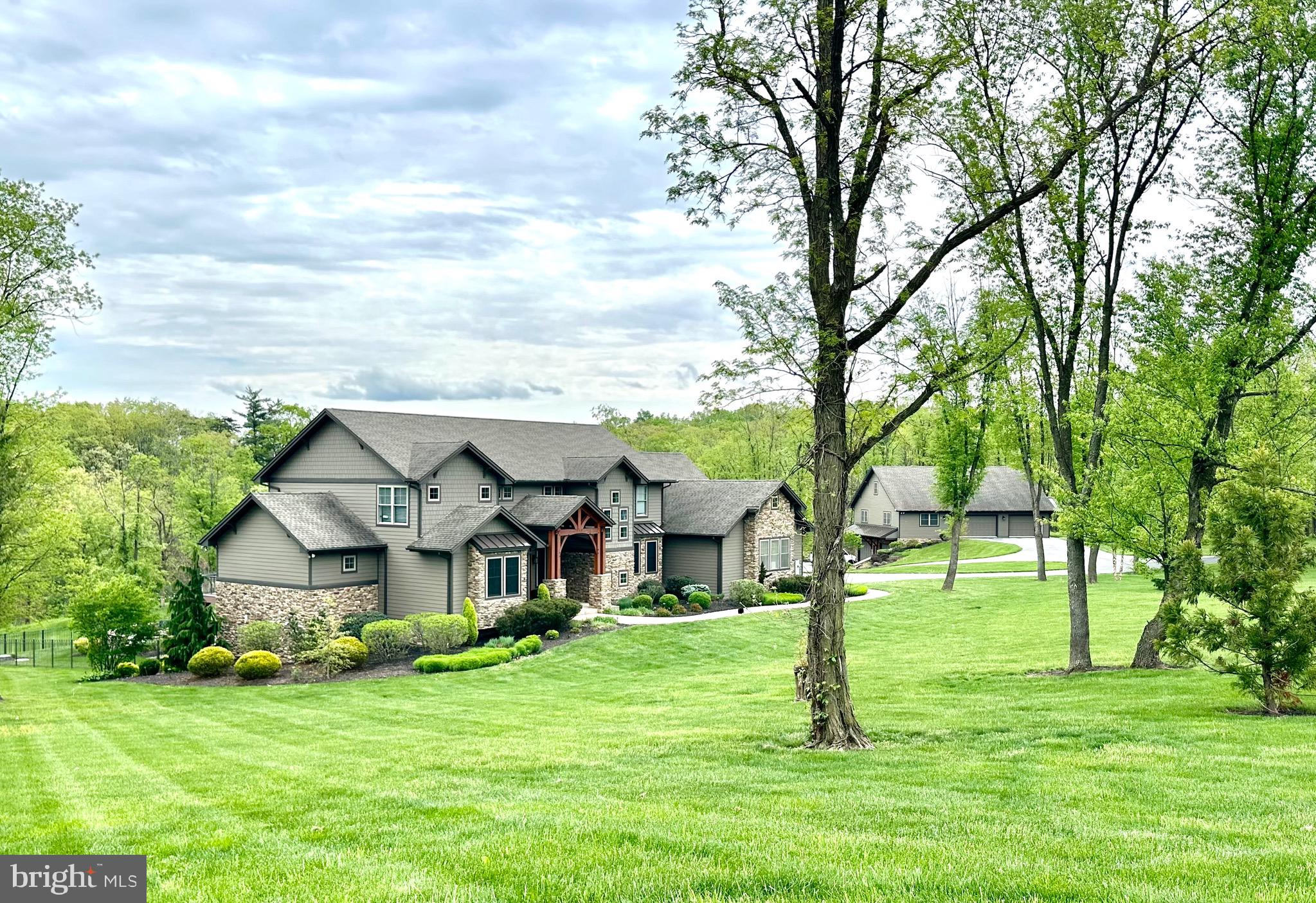 This one of a kind, custom home is nestled on a sprawling 19+ acres.  You are welcomed by a grand wood-framed entryway that sets the tone for the exceptional features found throughout this remarkable property.  The home's warm, organic aesthetic perfectly complements the breathtaking backdrop of the rolling hills and mature trees.  Expansive rear windows invited the outdoors in, allowing you to appreciate the beauty of the landscape and soak up the serenity of nature in every season. Open main-level living with soaring ceilings features a separate dining and living space along with spacious first-floor primary suite complete with a luxurious en-suite bath and large walk in closet, along with a beautifully designed custom kitchen that serves as the heart of the home.  Conveniently located on the main floor is your first of 2 laundry spaces, a nice office tucked away from the main living space and a large half bath.  Step out from your dining space, through the sliding doors and you'll find the showpiece of the home.  A grand, back deck made for relaxation and entertaining. With a dramatic covered section and cozy gas fire pit, it's the ideal place to take in the views, and enjoy the peacefulness of the property.  Ascend up the beautiful staircase to a large open area perfect for so many activities- this would be a great TV space for the kids, a crafting area; add desks and bean bags for a spot to chill and do homework or read a good book.  The 2 bedrooms both have their own en-suite baths and walk in closets with floating organizers.  The large room on the other side of the home is ideal for your 3rd upstairs bedroom.  Also a bonus, your 2nd laundry area is up here as well making it oh so convenient for everyone in the house!  Let's descend to the lower level, which is the true gem of the home.  Just a stove shy of having a full kitchen, you'll enjoy being belly up to the bar- which is a stunning granite countertop- and enjoy those moments with family and friends down here.  A full size refrigerator, dishwasher, microwave, stunning custom cabinets, pantry and so much storage.  The high ceilings make this space feel so open and inviting.  A large room off to the side can be used for whatever you desire.  Home gym, another bedroom, office- the possibilities are limitless.  A lovely guest bedroom, full bath and tons of storage complete the rooms in the basement.  Walkout to your own piece of paradise that is the paver patio.  With a built in fire pit, outdoor kitchen, mounted tv- all you have to do is add the hot tub to complete the package.   A large workshop/outbuilding gives room for all of your hobbies, with a finished lower level garage, built in air compressor and pressure washer.  There is nothing these owners didn't think of.  No expense was spared and everything was completed meticulously with lots of thought and love.  A barn with stables and pasture complete the other side of the property along with a small chicken coop and greenhouse.  This is every nature lovers dream.  A true staycation, that you'll never want to leave!