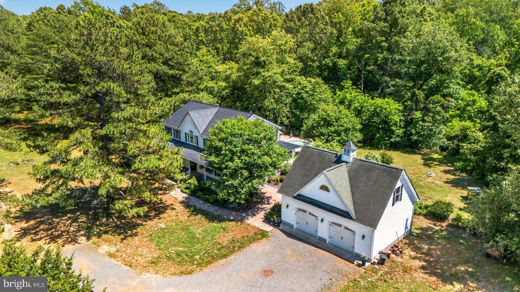 Rare opportunity to own a breathtaking Horse Farm that features an exquisite custom farmhouse on 21.95 breathtaking acres just 2 miles from downtown Leonardtown! This unbelievable location offers the perfect balance of privacy and convenience with easy access to schools, shopping, restaurants, coffee shops, and commuter routes while enjoying the peace and tranquility of country living. The picturesque property backs to McIntosh Creek with a private path leading to the creek and offers incredible opportunities for horseback riding, hunting, wildlife watching, and outdoor recreation. The meticulously maintained property features scenic fenced horse pastures, approximately 4 acres of RAMM vinyl horse fencing, private riding trail access just .25 miles from the home, and dirt road accessibility ideal for equestrian enthusiasts. Enjoy peaceful mornings and stunning countryside views from the inviting wraparound front porch overlooking the large, beautiful horse pasture, chicken coops, and gorgeous landscaping with stone walkways. The stunning custom farmhouse offers approximately 2,934 square feet with 4 bedrooms and 3.5 bathrooms filled with character, charm, and extensive updates throughout. The beautifully remodeled kitchen (2015) features granite countertops, custom tiled backsplash, gas stove, custom reproduction lighting, and a truly one-of-a-kind antique railroad baggage cart island. Gorgeous wood flooring, custom farmhouse boxed wood painted wall moldings, and a coffered dining room ceiling add timeless elegance and warmth. The spacious great room was remodeled in 2015 and showcases an oversized ceiling fan, stone fireplace, and Vermont Castings propane stove. The light-filled sunroom/den with bamboo flooring provides the perfect flex space to relax and enjoy scenic views of the property. Upstairs, the large loft area overlooking the family room offers endless possibilities for a home office, homeschool area, craft room, or additional living space.  A main floor Primary Suite and a larger upper Primary Suite. The upper primary suite and was completely remodeled in 2015 and features heated stone flooring, an incredible oversized tiled shower with dual shower heads, custom vanities, and a walk-in cedar closet. The upstairs hall bathroom was also beautifully remodeled in 2015. Additional features include custom closets throughout, upstairs secondary bedrooms with vinyl plank flooring, updated main level half bath with new vanity and cork flooring, WiFi thermostats, whole house surge protector (2026), Generac generator (2018), water heater (2016), and an upgraded American Standard HVAC system with propane backup (2017).  Outdoor living is equally impressive with intentional stone walk-ways, a gorgeous solar-heated Latham fiberglass inground pool surrounded by flagstone patio and metal fencing. Additional improvements include a flagstone back patio (2016), buried owned 500-gallon propane tank (2016), and durable metal roof on the house (2019).  Farm and outbuilding features include an oversized detached 2-car garage with full upper-level storage, metal barn/stable with two box stalls with water and electric, a large approximate 4 acre, fenced horse pasture, chicken coops, fenced animal pen, private driveway, and a temperature-controlled unfinished basement utility/storage room with outside only access. This is what you have been waiting for an extraordinary opportunity to own a beautifully updated farmhouse and your dream farm property in a sought-after Leonardtown location!