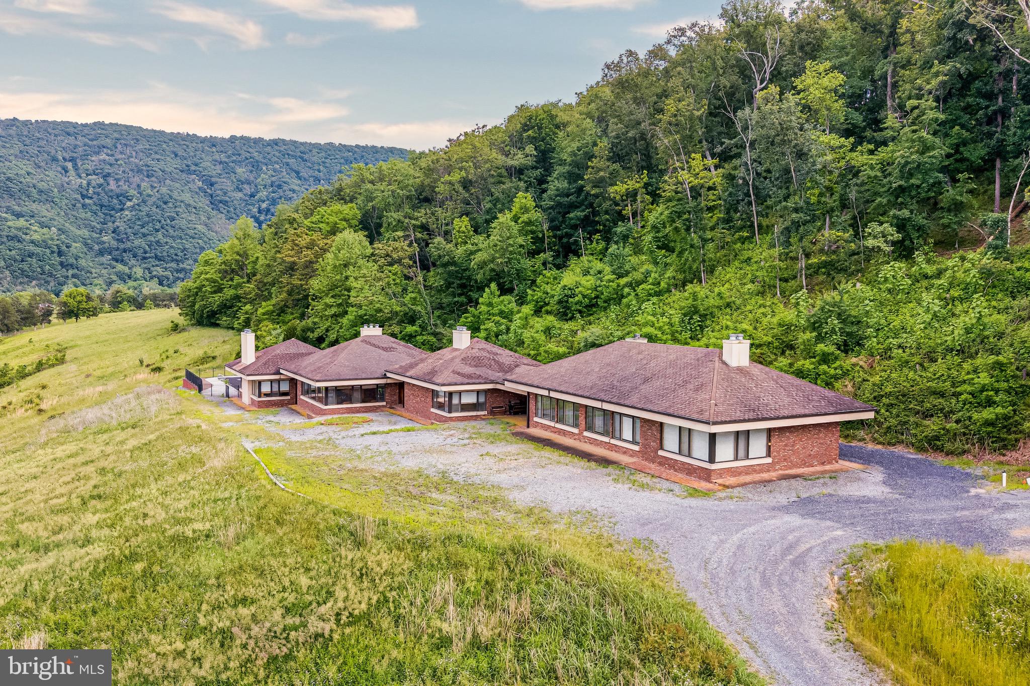 Experience the ultimate in privacy, recreation, and natural beauty on 66.58 spectacular acres overlooking the North Fork of the Shenandoah River. Surrounded by breathtaking mountain views, mature woodlands, and rolling countryside, this extraordinary property offers a rare opportunity to own a private retreat with endless possibilities.
The expansive contemporary residence is designed for both comfortable living and large-scale gatherings. The main home features 4 bedrooms, 4 full baths, 2 half baths, spacious living and dining areas, a full kitchen, kitchenette, laundry room, and an in-ground pool with patio. An additional wing includes a dramatic great room with a stone fireplace, full kitchen, full bath, and flexible-use rooms ideal for guests, offices, or retreat accommodations. The detached 8-car garage offers extensive finished space, including a third kitchen, living area, loft, full bath, and additional rooms, providing exceptional versatility.
Outdoor enthusiasts will appreciate direct access to kayaking, fishing, hiking, biking, wildlife observation, and countless opportunities to enjoy the surrounding natural landscape. Two large parking areas accommodate 20+ vehicles, making the property ideal for entertaining, retreats, events, or multi-generational living.
Currently operated as a resort, villa, and religious retreat center, this unique estate presents outstanding potential as a private family compound, vacation retreat, event venue, agricultural operation, or investment property. Zoned A-1 Agricultural. 
Conveniently located less than 10 minutes from Route 11, I-81, and Shenandoah County Park, approximately 15 minutes from Woodstock, and only 90 minutes from Washington, D.C. and Dulles International Airport. A truly one-of-a-kind riverfront estate offering serenity, recreation, and limitless potential. Pool conveys strictly as-is.