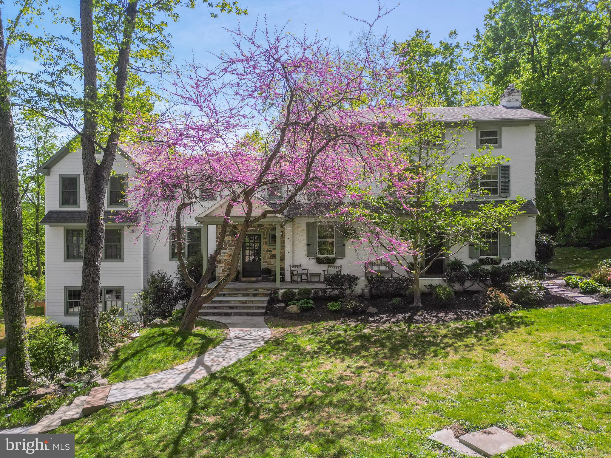 Set in Radnor Township, this 5-bedroom, 3-story farmhouse is a compelling blend of architectural legacy and thoughtful modern living. Originally built in 1846, the home began as a substantial farmhouse—part of the area’s deep agricultural roots—and evolved over the decades with additions that reflect the architectural styles of their time. The result is a home with depth, character, and integrity, unified by beautiful stonework, deep window sills, exposed interior stone walls, custom paneling, and wide-plank floors.
The current owner, a skilled craftsman, has guided the home's updates with an expert hand and a discerning eye. At the center of daily life is a bright, white kitchen, anchored by a striking navy blue seated island and outfitted with a suite of high-end appliances. This space flows seamlessly into a casual dining area and a stunning family room wrapped in three walls of oversized windows. Bathed in natural light throughout the day, this open, airy space has become the heart of the home.
For quieter moments, a warm and moody library/den is tucked off one of the home’s two foyers—a perfect setting for focused work, reading, or relaxed fireside evenings. The second foyer, styled with a shiplap ceiling, stone flooring, and an exposed stone wall, draws attention to one of the home’s original exterior windows—now a unique and charming interior feature that speaks to the property's layered history.
Just beyond the more formal of the two entries lies what was once the original parlor—now styled as a refined sitting room that transitions easily to a formal dining space when the occasion calls. The room’s generous proportions and architectural detail allow it to function beautifully in both roles.
A separate bar room adds yet another distinctive feature. Here, a brick-surround fireplace original to the home (now decorative) anchors the space, while expansive prep counters and glass display cabinetry make it both functional and visually striking—a space equally suited to entertaining or everyday elegance.
Upstairs, the primary suite offers quiet luxury, with wide-plank floors, spacious closets, and deep window sills that flood the room with soft natural light. The en-suite bath features a large walk-in shower, double vanities, and custom finishes that elevate the space. Two additional bedrooms share a hall bath that’s a true showstopper—featuring an exposed stone wall, a custom vanity with a vessel sink, and warm wood flooring that highlights the home’s enduring farmhouse character. The third floor offers two more bedrooms and a full bath—ideal for guests, home office use, or flexible family living.
Located within the top-ranked Radnor Township School District, this home offers a rare opportunity to own a piece of local history—refined and reimagined for today’s lifestyle. With timeless materials, handcrafted finishes, and spaces that welcome both everyday living and elegant entertaining, this is a Main Line classic brought beautifully into the present.