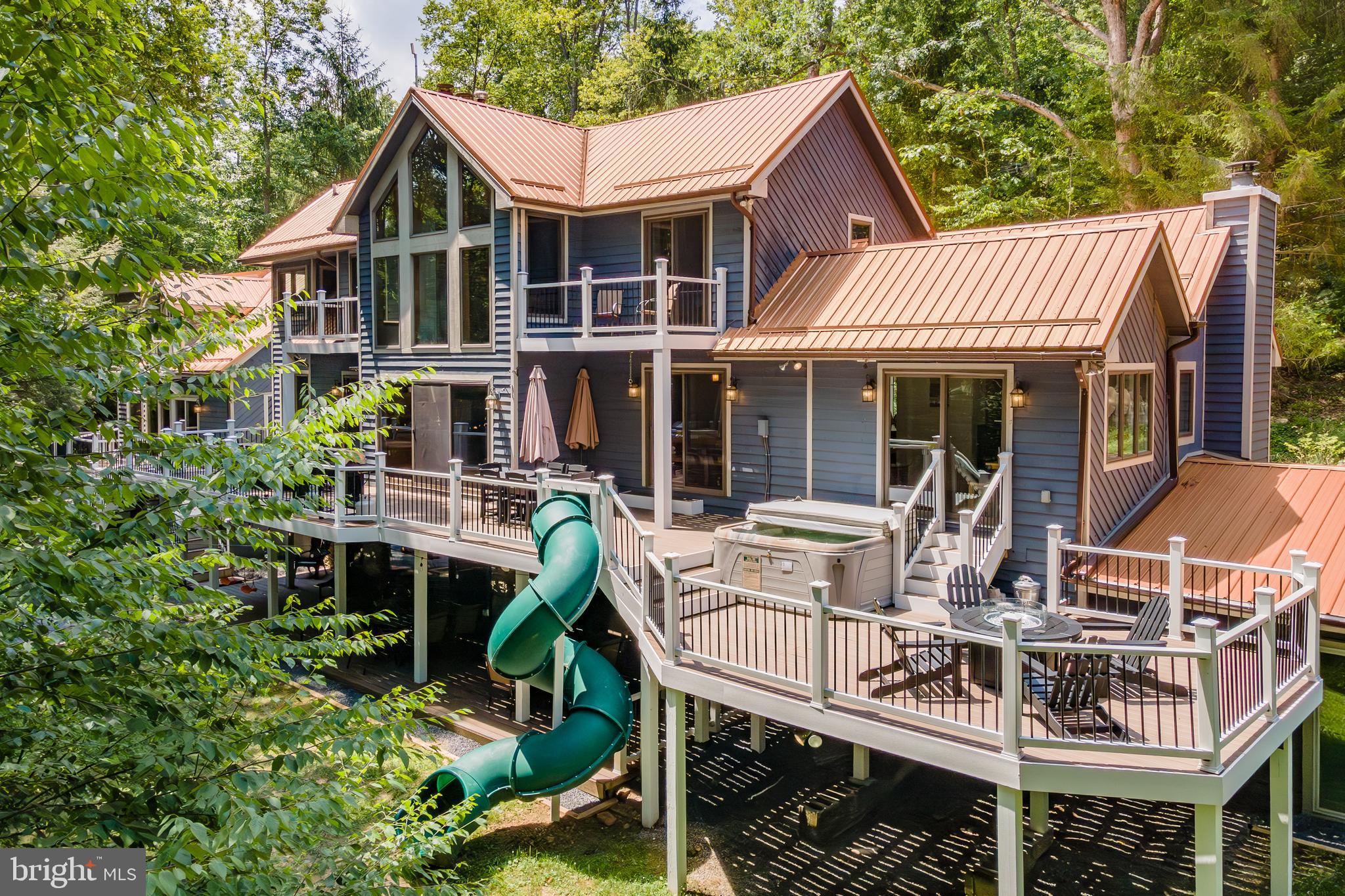 Iconic Lakeside Mountain Retreat at Deep Creek Lake! Recently Renovated, This 6 Bedroom 5.5 Bath Rental Goliath features a shiny new gourmet kitchen, updated bathrooms, several new mini split systems, a new hot tub, updated furnishings, a fresh coat of exterior stain, and new floors throughout. Complete facelift of the outdoor living space with sprawling new treks deck, fire pit, and concrete retaining wall. Multiple living/entertaining spaces, along with 3 true ensuites equipped with updated treks balconies. Boasting 7700 sq. ft, this house includes a 13-seat 150" Home Theater, indoor pool, several stacked stone fireplaces, and 3 stories of outdoor living space with a tube slide! Underground passage to the “detached” rec hall with a private in-law suite. A well-established Vacation Rental - Deep Creek's "Copper Canoe" generated $170k in 2023 and $161k in 2024 with over $50k on the books already for next year. Sold turnkey fully furnished and ready to go. Directly adjoining the community lake access, you'll enjoy one of Deep Creek's most peaceful and sought-after locations... Red Run Cove! Community Dock slip included. Minutes from restaurants, state parks, and WISP Resort, this timeless chalet offers everything the mountain lake life has to offer. Call today for details!