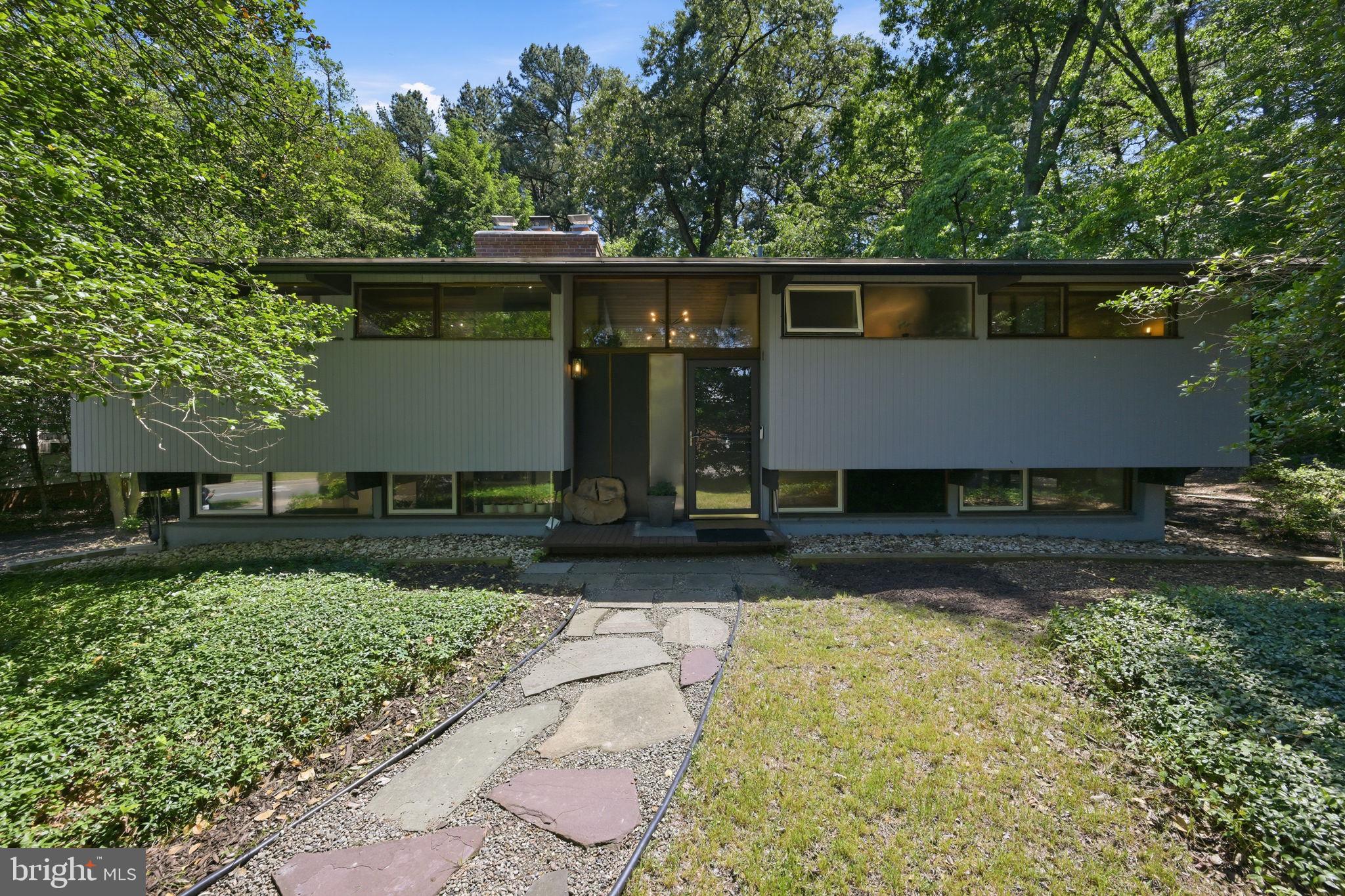 Nestled among the trees and backing to the University of Maryland Golf Course, this exceptional contemporary retreat offers the perfect blend of privacy, nature, and modern convenience. With 5 bedrooms, 2 full baths, 2 fireplaces, soaring cathedral ceilings with exposed beams, and an inviting indoor-outdoor design, this one-of-a-kind property is designed for both everyday living and effortless entertaining.

The upper level showcases a stunning open-concept living space filled with natural light. A gourmet kitchen features quartz countertops, a large center island, beverage refrigerator, and picturesque views of the surrounding tree sanctuary. Floor-to-ceiling glass doors connect the great room to an expansive renovated deck, creating a seamless flow between indoor and outdoor living while providing the perfect setting to entertain or simply enjoy the peaceful wooded backdrop.

Also on the main level are two spacious bedrooms and a beautifully renovated spa-inspired bathroom featuring a Restoration Hardware vanity with marble countertops, Signature Hardware fixtures, and a designer walk-in shower.

The walk-out lower level offers three additional bedrooms, a second fireplace, an updated full bath, and a laundry/mudroom with new high-capacity washer and dryer. Sliding doors lead directly to a patio ideal for gatherings, outdoor dining, and relaxation.

Beyond the main residence sits a new shed and a fully renovated 625-square-foot detached studio with electricity & cooling.  Surrounded by nature, this versatile space is perfect as a home office, guest suite, fitness studio, or creative retreat.

Extensively improved in recent years, updates include a new roof and gutters (2022), split-system HVAC/heat pumps (2022), chimney restoration (2022), studio renovation (2023), new shed (2023), renovated main deck (2024), renovated studio deck (2024), new water heater (2025), high-capacity washer and dryer (2025), Bali blinds throughout, Google Nest security cameras, and an integrated alarm system.

Ideally located just behind the University of Maryland campus, this remarkable property offers direct access to the scenic Paint Branch Trail for walking, running, and biking. Enjoy nearby cultural events at the Clarice Smith Performing Arts Center, Big Ten athletics, university fitness facilities, community pool, Whole Foods, Trader Joe's, and the restaurants and shops of Old Town College Park. Commuters will appreciate easy access to major roadways, the new Purple Line, Washington, D.C., and both BWI and Reagan National airports.

A rare opportunity to own a thoughtfully updated contemporary home with unmatched natural surroundings, flexible living spaces, and a premier College Park location.