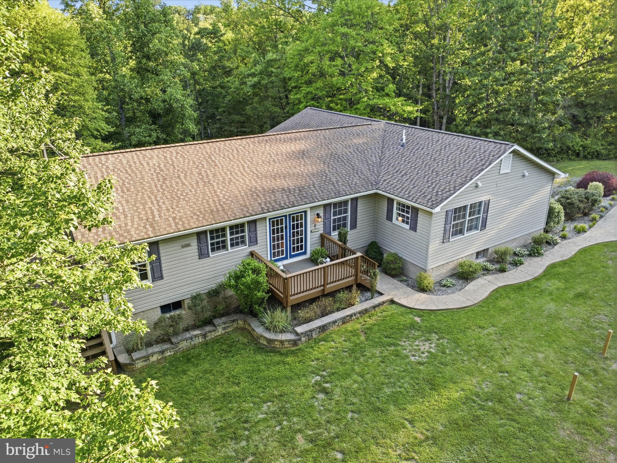 This charming home on over 6 acres of partially wooded property with a meandering stream offers privacy and the calming effects of nature. The 5 bed, 3.5 bath home affords main level living, with the added bonus of extra living space in the large walkout basement. The upstairs of this ranch home, with its beautiful hardwood floors, features an open, expansive kitchen and dining room layout, with plentiful cabinet and counter space, plus room for an island! Real wood cabinets, granite countertops and breakfast bar seating elevate the look of the kitchen, and make it a space you will love to spend hours entertaining in! The half bath is conveniently located at the end of the kitchen near one of numerous entrances to the wraparound deck. The spacious living room allows for large social gatherings, or a quiet evening at home enjoying the solitude. One primary suite and two generously sized secondary bedrooms, plus the second (and large!) full bathroom, are located down the hall. The primary suite has a double vanity, separate shower and toilet room and plenty of closet space. A fourth main level bedroom is located off the living room, with its own entrance to the primary bedroom, making it a fantastic flex space that could be also be used as an office or craft room! Head downstairs to more flexible space to be used in whatever way suites your needs best! A family room with french doors leading to outside and a full bedroom and bathroom have new luxury vinyl plank flooring for easy cleaning and room for guests! The equally large, unfinished side of the full basement is open to your creativity. With another set of exterior french doors and two large windows allowing for extra light, you can use your imagination to dream up a game room, exercise room or use for whatever your hobby may be! As if that doesn't seem like an overabundance of space, there is yet ANOTHER unfinished storage room on the lower level. Back outside, enjoy the forest views from your wraparound deck, while embracing the country life in your yard with room for potential livestock or poultry and gardens! Is tinkering in a workshop more your thing? You're in luck! With a 28x30 oversized garage with staircase to a full second-story storage area, the possibilities are endless. There is even existing ductwork in place for those more heavy-duty projects. Be sure to get your showing scheduled so you don't miss out on this opportunity!