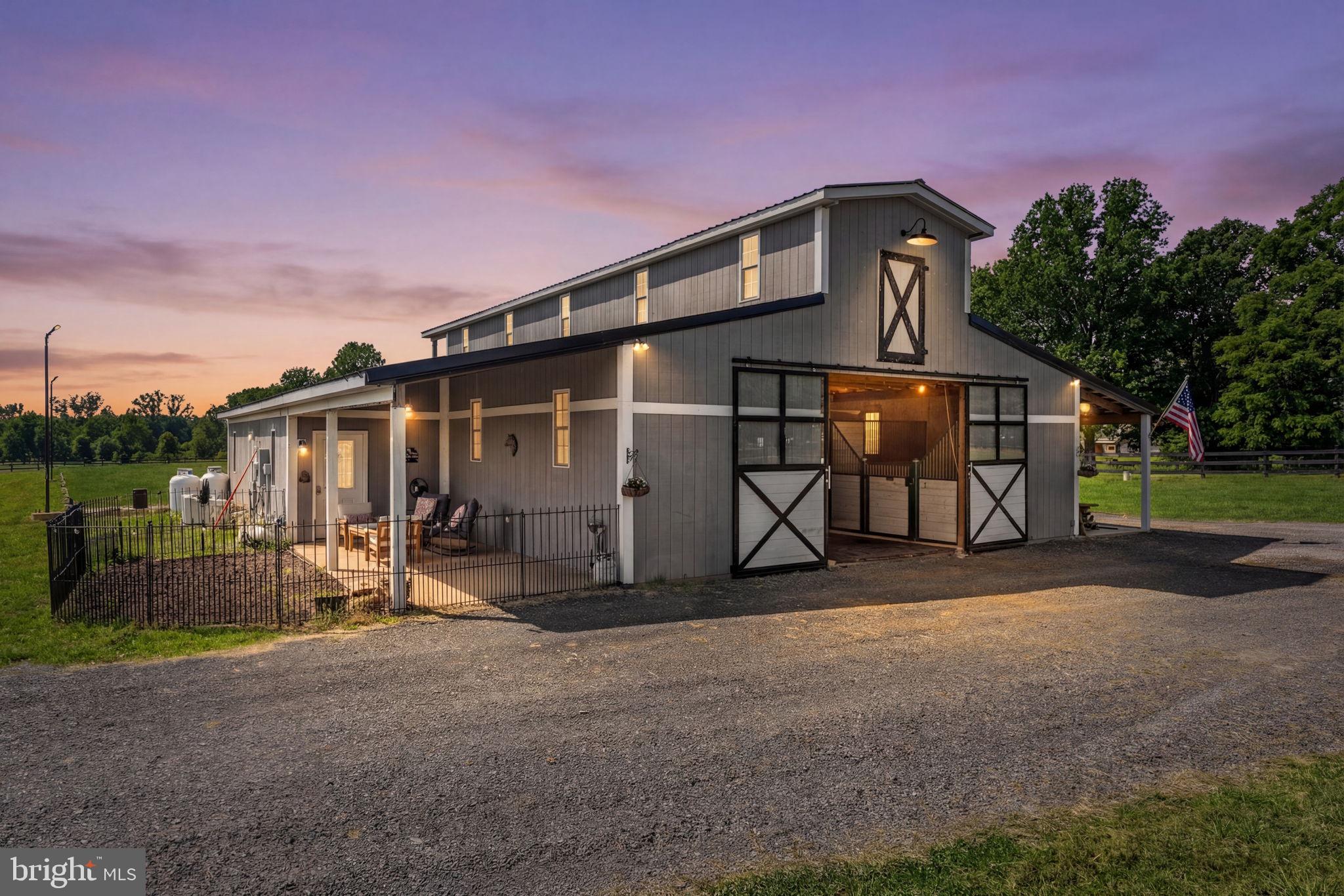 Welcome to WhiteCliff Farm! Completed in 2022, this turnkey 8-acre equestrian facility in northern Culpeper County offers serious horse infrastructure in a convenient location—approximately 25 minutes to Warrenton, 15 minutes to Culpeper, and about one hour to Dulles International Airport—with the option to build a home on the property if desired. An automatic privacy gate (operable by keypad, remote, or phone app) welcomes you from a hardtop road to a center-aisle barn on a full concrete slab, featuring six 12x12 interior stalls with mattresses and custom American Stalls fronts, plus two 10x12 exterior guest stalls. The barn includes rubber pavers in the aisle, WiFi cameras (four stalls and barn front), WiFi-enabled smoke detectors, fly spray dispensers with refillable canisters, a fully finished office/tack room with full bath and kitchenette, and a heated feed room with washer, dryer, and particulate filter on the well, all backed up by a Generac generator. Horses benefit from heated automatic waterers in the pastures, a wash rack with hot/cold water, and a solarium heat light in the wash area, while all drive areas are constructed over geotextile for durability. The 100x200 arena is professionally built with geotextile, #2 stone crush, bluestone, and beautiful golden angular sand, illuminated by LED lights for evening rides and prepped with conduit and a hydrant in place for a future arena watering system. Truly a horse lover’s paradise, WhiteCliff Farm is ready for a new steward who wants the ultimate in luxury for their horses and themselves.