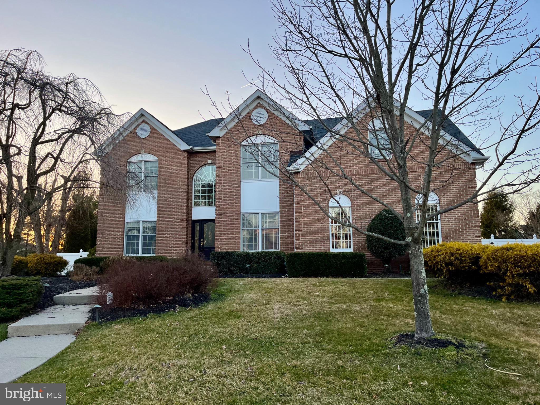 Welcome to this impressive 4-bedroom, 2.5-bath Colonial, distinguished by its stately brick façade, striking rooflines, and dramatic arched windows. Set amid mature landscaping, this Yardley residence blends timeless elegance with thoughtfully designed living spaces and a private backyard retreat. Step into the dramatic two-story foyer, where a sweeping staircase, rich Brazilian walnut hardwood floors, and abundant natural light set the tone for elegant spaces beyond. Double doors open to a private home office, while the formal living and dining rooms flow seamlessly together, showcasing architectural columns, wainscoting, crown molding, and a sun-filled bay window.The spacious eat-in kitchen is beautifully appointed with 42-inch custom cabinetry, granite countertops, a center island with a gas cooktop, and a wall of windows overlooking the pool and backyard. Open to the kitchen, the impressive family room features soaring cathedral ceilings, a stone-front wood-burning fireplace, and a dramatic second staircase rising to an open upper-level balcony, a striking architectural focal point that also provides convenient secondary access upstairs. A powder room and dedicated laundry/mudroom complete the main level. Upstairs, the spacious primary suite offers double-door entry, a sitting area, separate dressing vanity, generous walk-in closet, and an en-suite bath. Three additional generously sized bedrooms share a well-appointed hall bath. The basement provides flexible space for a recreation room, home gym, media room, or additional storage. Designed for year-round enjoyment, the private backyard features a spacious deck overlooking the heated in-ground gunite pool, along with two distinct patio areas offering plenty of space for outdoor dining, lounging, and entertaining. A fenced yard completes this inviting and secluded outdoor retreat. Ideally located in the highly desirable Yardley area within the Pennsbury School District, this home offers excellent commuter access to I-95, I-295, Route 1, and the nearby SEPTA train station.