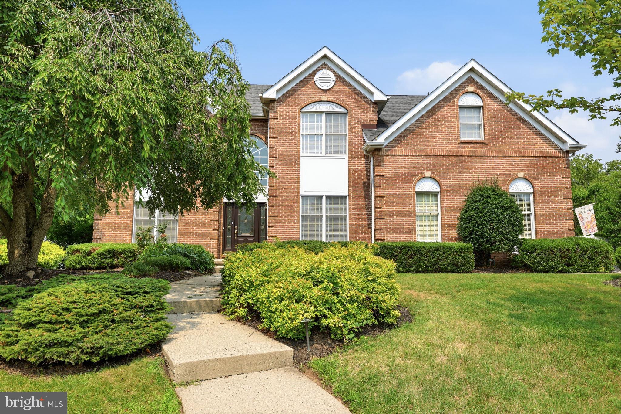 Welcome to this impressive 4-bedroom, 2.5-bath Colonial, distinguished by its stately brick façade, striking rooflines, and dramatic arched windows. Set amid mature landscaping, this Yardley residence blends timeless elegance with thoughtfully designed living spaces and a private backyard retreat. Step into the dramatic two-story foyer, where a sweeping staircase, rich Brazilian walnut hardwood floors, and abundant natural light set the tone for elegant spaces beyond. Double doors open to a private home office, while the formal living and dining rooms flow seamlessly together, showcasing architectural columns, wainscoting, crown molding, and a sun-filled bay window.The spacious eat-in kitchen is beautifully appointed with 42-inch custom cabinetry, granite countertops, a center island with a gas cooktop, and a wall of windows overlooking the pool and backyard. Open to the kitchen, the impressive family room features soaring cathedral ceilings, a stone-front wood-burning fireplace, and a dramatic second staircase rising to an open upper-level balcony, a striking architectural focal point that also provides convenient secondary access upstairs. A powder room and dedicated laundry/mudroom complete the main level. Upstairs, the spacious primary suite offers double-door entry, a sitting area, separate dressing vanity, generous walk-in closet, and an en-suite bath. Three additional generously sized bedrooms share a well-appointed hall bath. The basement provides flexible space for a recreation room, home gym, media room, or additional storage. Designed for year-round enjoyment, the private backyard features a spacious deck overlooking the heated in-ground gunite pool, along with two distinct patio areas offering plenty of space for outdoor dining, lounging, and entertaining. A fenced yard completes this inviting and secluded outdoor retreat. Ideally located in the highly desirable Yardley area within the Pennsbury School District, this home offers excellent commuter access to I-95, I-295, Route 1, and the nearby SEPTA train station.