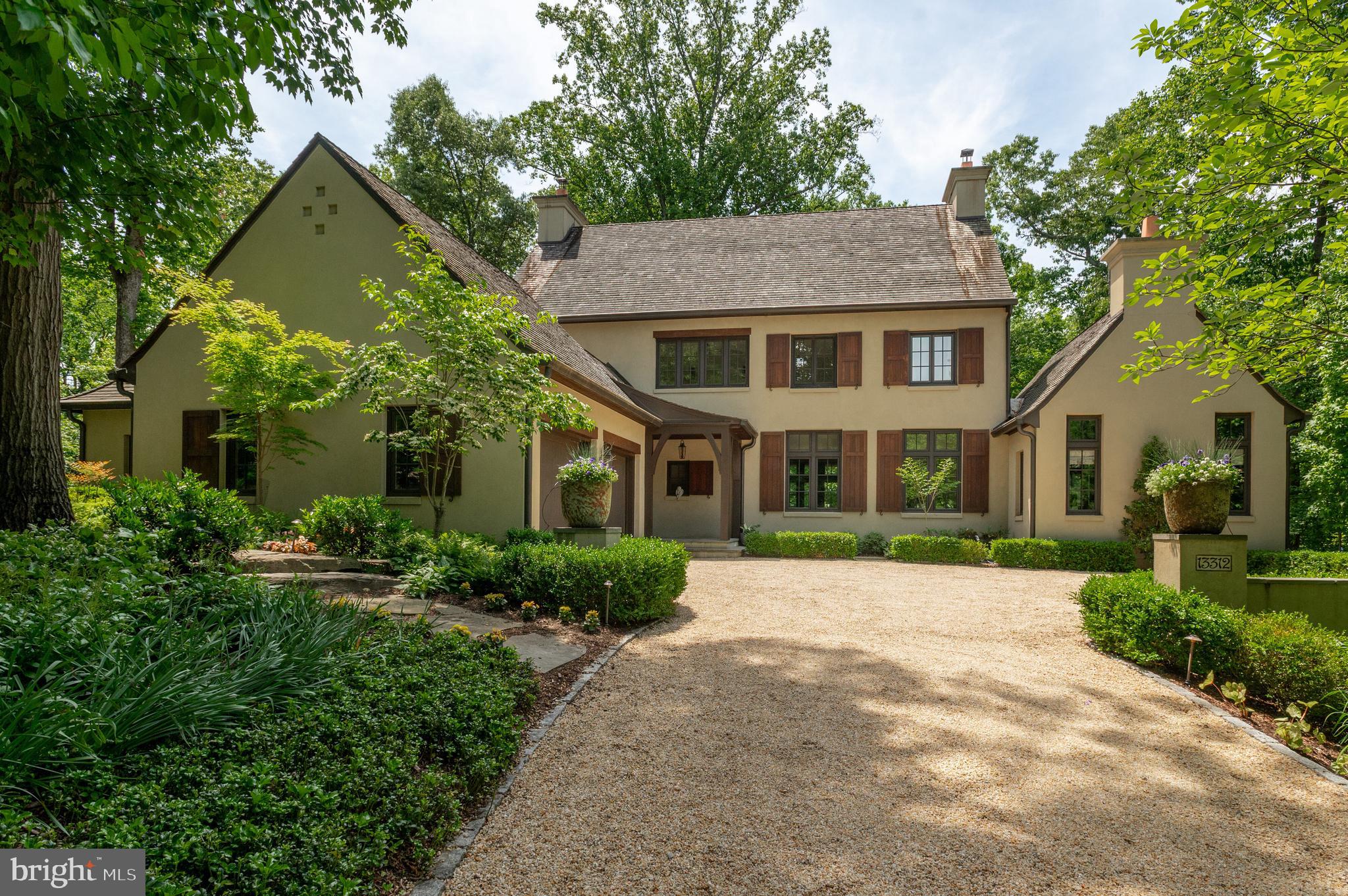 New Price Improvement! Nestled in the serene woodlands of prestigious Merry-Go-Round Farm, Drew Cottage is a one-of-a-kind architectural gem by award-winning architect Jim Rill, combining timeless European country charm with exceptional craftsmanship and modern functionality. This stunning residence offers an unparalleled lifestyle with breathtaking indoor and outdoor living spaces including four bedrooms and four and a half bathrooms.
Set against the backdrop of conservation land, this home welcomes you with a charming flagstone foyer that serves as an interior breezeway, connecting the stately front portico to the rear terrace. From here, step into a grand great room featuring 10.5-foot mahogany-beamed ceilings, a limestone Rumsford fireplace, and three sets of French doors that open onto a 40-foot terrace overlooking the private, wooded backyard.The living area is open to the dining area, perfect for entertaining and informal living.
Thoughtfully designed for both relaxed living and sophisticated entertaining, the heart of the home includes a sun-drenched eat-in chef’s kitchen with custom cabinetry, 2-inch Carrera marble countertops, Thermador appliances, Induction cooktop, double ovens, prep sink, and a spacious pantry. Adjacent is an atrium-style breakfast room with floor-to-ceiling windows offering captivating views of Merry Go Round Farm’s tranquil ponds and pastures.The library highlights a cathedral ceiling, built-in bookcases, window seats, and a second Rumsford fireplace. Completing the main level are the mudroom, elegant renovated powder room, large laundry room, and wide plank white oak flooring throughout.
Upstairs, the primary suite is a peaceful retreat with French doors opening to a private balcony, a generous custom walk-in closet, and a luxurious recently updated spa-like ensuite featuring dual vanities and an oversized walk-in shower and a soaking tub. Two additional upper-level bedrooms and bathrooms offer abundant natural light and classic casement windows.The walkout lower level includes a spacious family room with marble wet bar and custom built-ins, an exercise room, children’s playroom or in-law suite potential, and a large bedroom that opens to a covered patio/Lanai with woodland views. This level also includes a full bath, an immaculate utility room, and ample storage space.
Architectural details throughout the home reflect French country influence with arched doorways, rounded wall corners, pocket doors, casement windows, and extra-thick exterior walls. High-end finishes extend outdoors with authentic three-coat stucco, clay chimney pots, cedar roof and shutters, mahogany porch ceilings, and a beautifully integrated hardscape featuring flagstone patios, flat yard, a cedar pergola, and pea gravel sitting areas. Modern conveniences abound with geothermal dual-zone heating and cooling, Sonos sound system, wireless security, fire sprinkler system, water filtration, and whole-house surge protection. The three-car garage and extensive storage areas complete this exquisite property. A true harmony of elegance, innovation, and natural beauty, Drew Cottage is one of Merry Go Round Farm’s most remarkable homes.