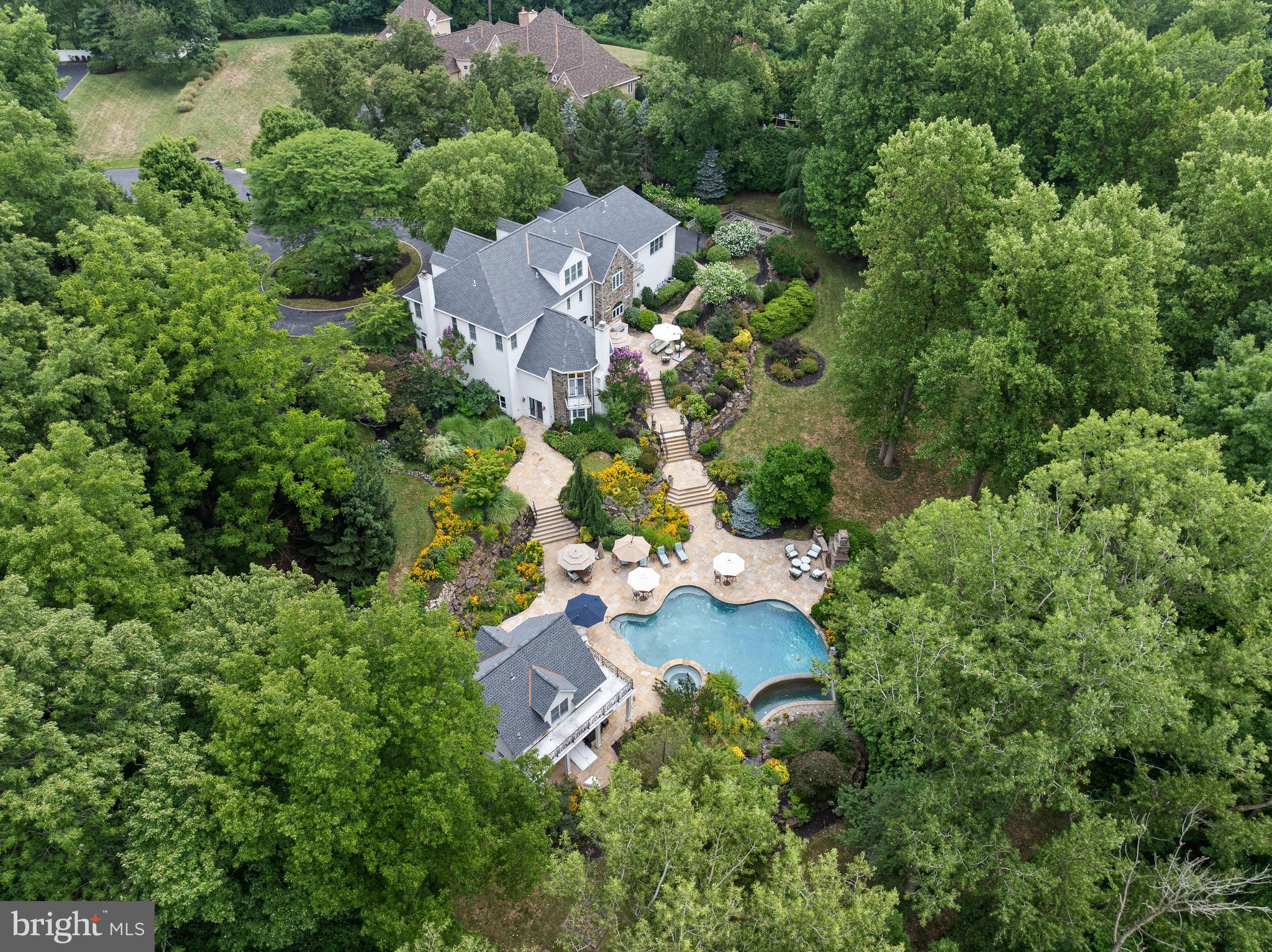 Be still my heart on Harts Ln... Escape to paradise at this luxury 10-acre estate on a private cul-de-sac in Whitemarsh Township.  This one-of-a-kind property is a serene retreat where every day feels like a getaway, complete with luxurious amenities, stunning views, and a relaxing ambiance. It's a place where the rest of the world fades away, and you're enveloped in comfort and tranquility.  The main house boasts over 8,000 square feet of living space, complete with 6 bedrooms,  6 full baths, a fully-finished walk out basement, a 4-car garage, and a spectacular backyard oasis.  Also included on the compound is a 1,900 square foot guest house, perfect for multi-generational living, a caretaker/au-pair, or a private retreat for your house guests. The guest house features a living room, full kitchen, main floor full bathroom, and 2nd floor bedroom & ensuite bathroom. There is also a full basement for storage, outdoor bar & grill for entertaining, and a wrap-around balcony to take in all of the beautiful sights and sounds of the peaceful backyard. Immediately surrounding the home, you’ll find 3 fenced acres with an infinity pool, hot tub, Tennessee flagstone terraces, outdoor fireplace, flat grass backyard, horseshoe pit, vegetable garden, and extensive landscaping.  Close your eyes and imagine this home being the place where all of your friends & family want to gather.  Designed to evoke your sensory experiences, this backyard oasis is unmatched in attention to detail.  Take in the sounds of the waterfall, chirping birds, mermaid fountain, and cracking fire in the outdoor fireplace.  In the distance you can hear the clang of a horseshoe and a good friend’s laughter.  Smell the delicious food simmering on the grill.  Stroll the grounds to admire the colorful flowers and cozy ambience of exterior lighting. When you’re here, time slows down and you’re able to be fully present with your loved ones. 
Beyond the estate fence is another 7 protected acres, mostly wooded to provide the ultimate privacy.  Gracing the entrance of the main house is a koi pond with waterfall, a metaphorical exhale, creating instant zen.  Step inside and you’ll be greeted by the grand foyer with 3-story turned staircase and custom wrought iron railings.  This home exudes timeless elegance with its classic architectural details, refined finishes, and sophisticated design. The interior seamlessly blends traditional charm with modern luxury, featuring high ceilings, intricate moldings, and carefully curated materials. Every room offers an enduring style that transcends passing trends.  At this property, the best of both worlds converge: Old world charm meets modern conveniences. Details such as extensive woodwork & trim, custom built-ins, walls of windows, charming fireplaces, gorgeous wrought iron railings & gates, add character and evoke another time, while modern conveniences like central surround sound, a biometric security system, temperature controlled wine cellar, and back-up generator ensure your ultimate comfort. The home has current upgrades/enhancements including: Brand new roof & gutters on both dwellings, replaced in 2023 with 25 year warranty/50 on materials; new kitchen appliances in 2020 including SubZero Professional freezer/refrigerator; new carpet on all stairs in main house, basement & owners suite in 2023; freshly painted owners suite 2023; new well pump in 2022; Lutron lighting system; World Wide Stereo surround sound throughout the property, Murano glass chandeliers & light fixtures in dining room; dog washing station; 4-Zone HVAC (new HVAC 2nd floor in 2020, new HVAC 1st floor in 2023; 2 hot water tanks in main house with 1 replaced in 2020 & the other in 2015; temp-controlled wine cellar; Kohler back-up generator, irrigation system supported by its own well; and the list goes on! 2040 Harts Lane will satisfy all of your heart’s desires, and it’s an experience that one must see to truly believe.
