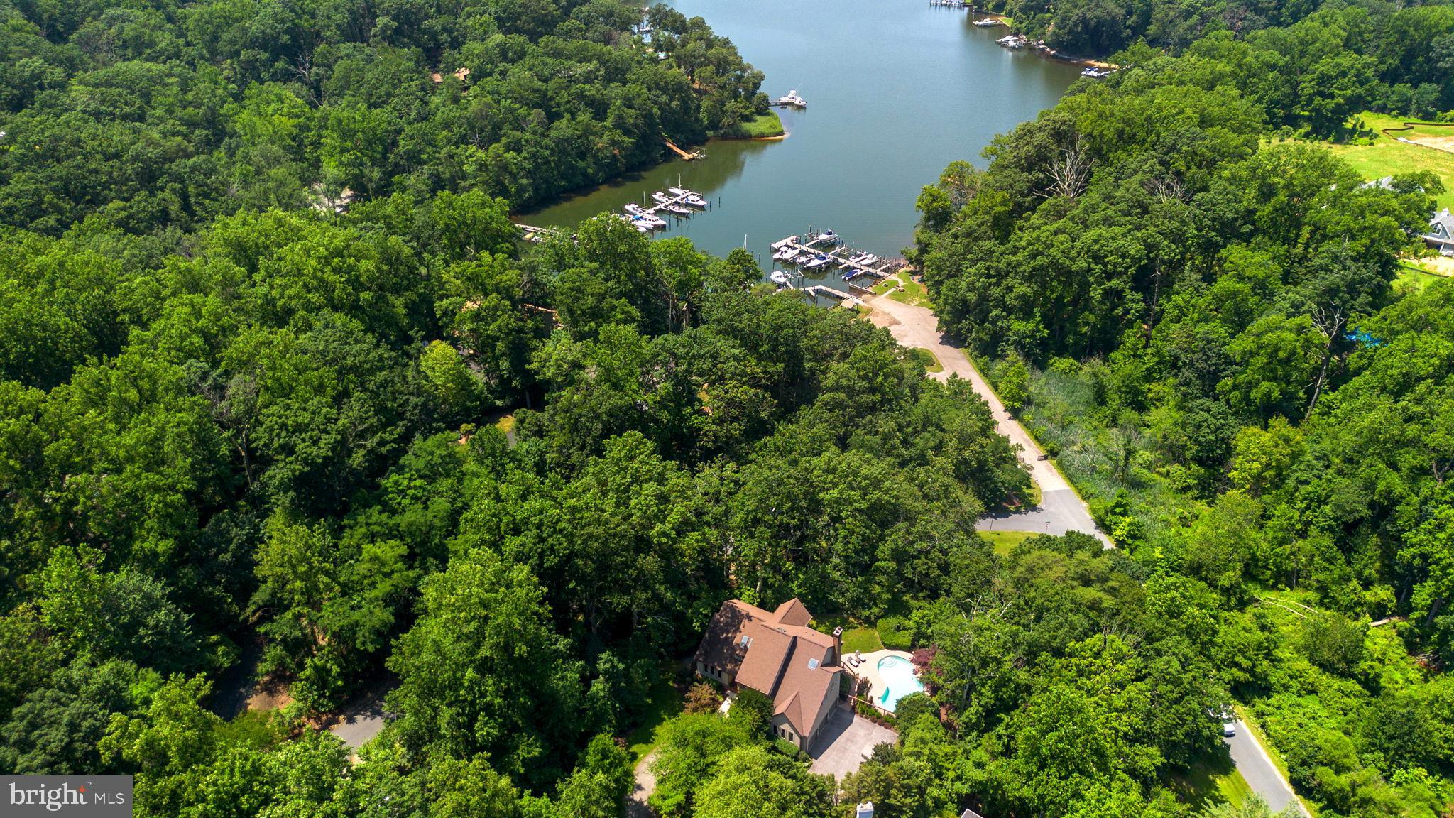 Welcome to this exceptional Stone & Cedar Home with a saltwater pool and water views in Severn View! Nestled on 1.42 wooded acres, this stunning contemporary home offers a rare combination of privacy, luxury, and water privileged living in the highly sought-after Severn View community. With breathtaking seasonal views of the Severn River across Asquith Creek, this 6-bedroom, 5-bathroom residence spans across three levels and is designed to impress. Upon entering through the grand two-story foyer, you're greeted by an open, airy layout with Brazilian walnut floors and abundant natural light. The spacious formal living and dining areas flow seamlessly into the recently remodeled gourmet kitchen (2016), featuring crisp white cabinetry, quartz countertops, a large island with seating, and top-tier appliances—ideal for any home chef. The adjoining family room, with its cozy wood-burning fireplace, offers a relaxing space to unwind. Step outside onto the expansive rear deck, accessible from both the dining and family rooms, where you can enjoy serene views of the saltwater pool, waterfall feature, and Asquith Creek. This is the perfect spot for entertaining or simply taking in the peaceful surroundings. The main floor also includes a versatile guest suite, currently used as a home office, along with a full bath—providing flexibility for family and guests. Upstairs, the primary suite is a true retreat. It boasts a private stone fireplace, a private balcony with stunning water views, and a beautifully renovated spa-like bathroom complete with a freestanding soaking tub, dual vanities, a walk-in shower, and an expansive walk-in closet. Three additional generously sized bedrooms and two full baths complete the upper level, ensuring ample space for family and guests. The finished lower level is an entertainer’s paradise. With direct access to the pool area, it includes a kitchenette, bedroom/exercise room, office, full bath, and a large recreational room—ideal for games, movies, or hobbies. The walk-out basement also provides easy access to the private backyard oasis and the secluded pool area. Additional highlights include a 3-car garage with soaring ceilings for maximum storage, a circular driveway, a playground area adjacent to the pool deck, and attic and crawl space storage. The community offers a wealth of amenities, including a newly renovated, gated waterfront with a pavilion, firepit, kayak storage, a boat ramp, piers, and your own deeded boat slip (#3) at the nearby marina. With award-winning schools, proximity to the B&A bike trail, and easy access to major commuter routes, this home combines luxury, comfort, and convenience in one extraordinary setting. Don’t miss the opportunity to make this rare property your own—schedule your private tour today!