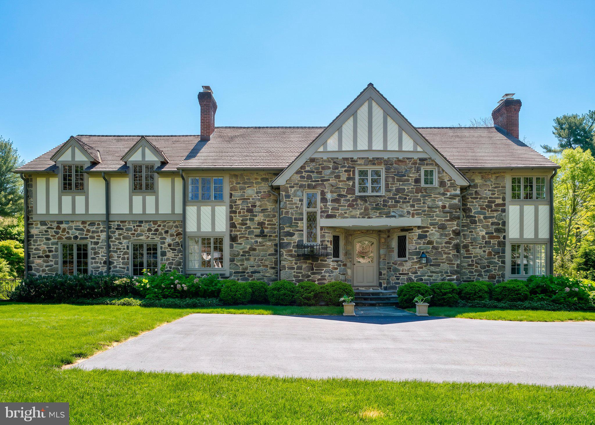 Set on the coveted north side of Bryn Mawr, this extraordinary Tudor revival is a masterful blend of timeless 1930s craftsmanship and sophisticated modern luxury. Meticulously restored and completely reimagined by Pinemar with design by Warren Claytor Architects, 617 Harriton Road is a one-of-a-kind residence offering over 3,800 square feet of beautifully curated living space in the award-winning Lower Merion School District. From the moment you arrive, the home’s architectural character is unforgettable. A striking exterior showcases hand-cut local stone, including rare touches of West Chester green serpentine and Wissahickon schist, creating a rich texture and presence rarely found today. The original oak front door with iron strap hinges opens into a gracious foyer where old-world charm meets refined contemporary living. Bathed in natural light throughout, the home’s flowing floor plan was designed for both elegant entertaining and everyday comfort. To the right, the dramatic formal living room features a soaring barrel ceiling and an ornate wood-burning fireplace that anchors the space with warmth and grandeur. French doors open directly to the terrace and grounds, creating seamless indoor-outdoor living. At the heart of the home is an exceptional chef’s kitchen, thoughtfully designed with custom cabinetry, quartz countertops, premium finishes, and an oversized island perfect for gathering. The adjoining family room and dining area create an effortless entertaining space, while expansive walls of windows and French doors frame views of the stunning outdoor setting. Step outside to the flagstone terrace and beautiful Paradigm pool, surrounded by lush landscaping and private lawn space that feels like a secluded retreat. One of the home’s most remarkable and unexpected features is the regulation-size Anderson squash court located just off the kitchen, a truly rare luxury. Whether used for squash, basketball, fitness training, yoga, pickleball practice, a wellness studio, or year-round recreation, this incredible space offers endless possibilities for all ages and lifestyles. A richly paneled library with custom built-ins and a charming corner fireplace provides the perfect setting for a home office, reading room, or intimate retreat. Throughout the first floor, impeccably maintained solid hardwood floors add warmth and authenticity. Original architectural details remain beautifully preserved, including solid wood interior doors, leaded diamond-motif windows, and wrought-iron Juliet balcony accents that subtly honor the home’s historic roots. The second floor is anchored by a luxurious primary suite featuring a spa-inspired bath with dual vanities, custom glass shower, water closet, and an oversized walk-in closet room. A private covered balcony offers a peaceful setting for morning coffee overlooking the beautifully landscaped grounds. Three additional bedrooms and a full bath provide flexibility for family, guests, or office space, while a conveniently located second-floor laundry adds modern practicality. Additional highlights include a new cedar shingle roof, whole-house generator, unfinished basement with perimeter drainage system, and countless thoughtful upgrades throughout. Ideally located within walking distance to Harriton House, the SEPTA Paoli/Thorndale Line train station, and the shops, dining, and amenities of the Village of Bryn Mawr, this turnkey residence offers an unmatched combination of architectural beauty, modern functionality, and premier Main Line living. 617 Harriton Road is more than a home... it is a rare opportunity to own a fully restored Tudor masterpiece with extraordinary amenities in one of the Main Line’s most desirable walkable neighborhoods.