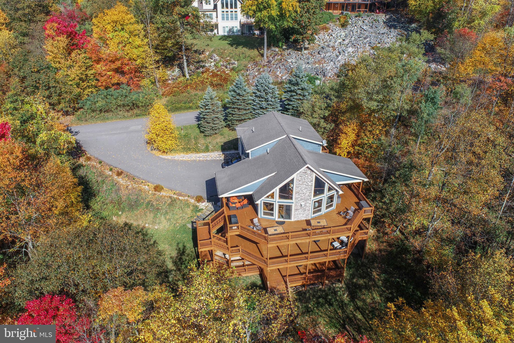 Mountain living meets the Deep Creek Lake lifestyle in this stunning five-bedroom, five-bath lake access retreat!  Offering dramatic architecture, generous living space, and a strong rental performance of $81,000 to $90,000.  The main level features soaring wood cathedral ceilings, a floor-to-ceiling stone fireplace to cozy up to after a day on the slopes, and a wall of glass in the open kitchen, dining, living areas.  The main level also includes two bedrooms and two full baths, one bath private to a bedroom, offering excellent flexibility for guests and main-level living.

The upper level is dedicated to a spacious primary suite with private deck, sitting area, walk-in closet, with a seperate area for owner lock up storage.  The spa like bath has a large jetted tub and a shower.  Just outside the bedroom is a loft overlooking the great room.

Lower Level one includes a spacious family room with a second stone fireplace and a wet bar, two bedrooms a full baths with a tub shower and a seperate shower.  A laundry room completes the picture.

Lower Level two offers a game room for family fun and an additional full bath.  Also a seperate room for storage, ski equipment, or owners lock up area. Step out to the hot tub to warm up and relax after skiing or being on the lake.

Enjoy wraparound decks on three levels with a covered dining and covered hot tub area. The lake access is minutes away with a clubhouse, picnic area, and swimming and kayaking on Deep Creek Lake. There is also a tennis court for the neighborhood! This home has an impressive annual rental income of $81,000–$90,000.  Located just five minutes from Deep Creek Lake State Park, and close to Wisp Ski Resort for four-season recreation! 

Call today to preview the many features this Mountain Lake Property has to offer!