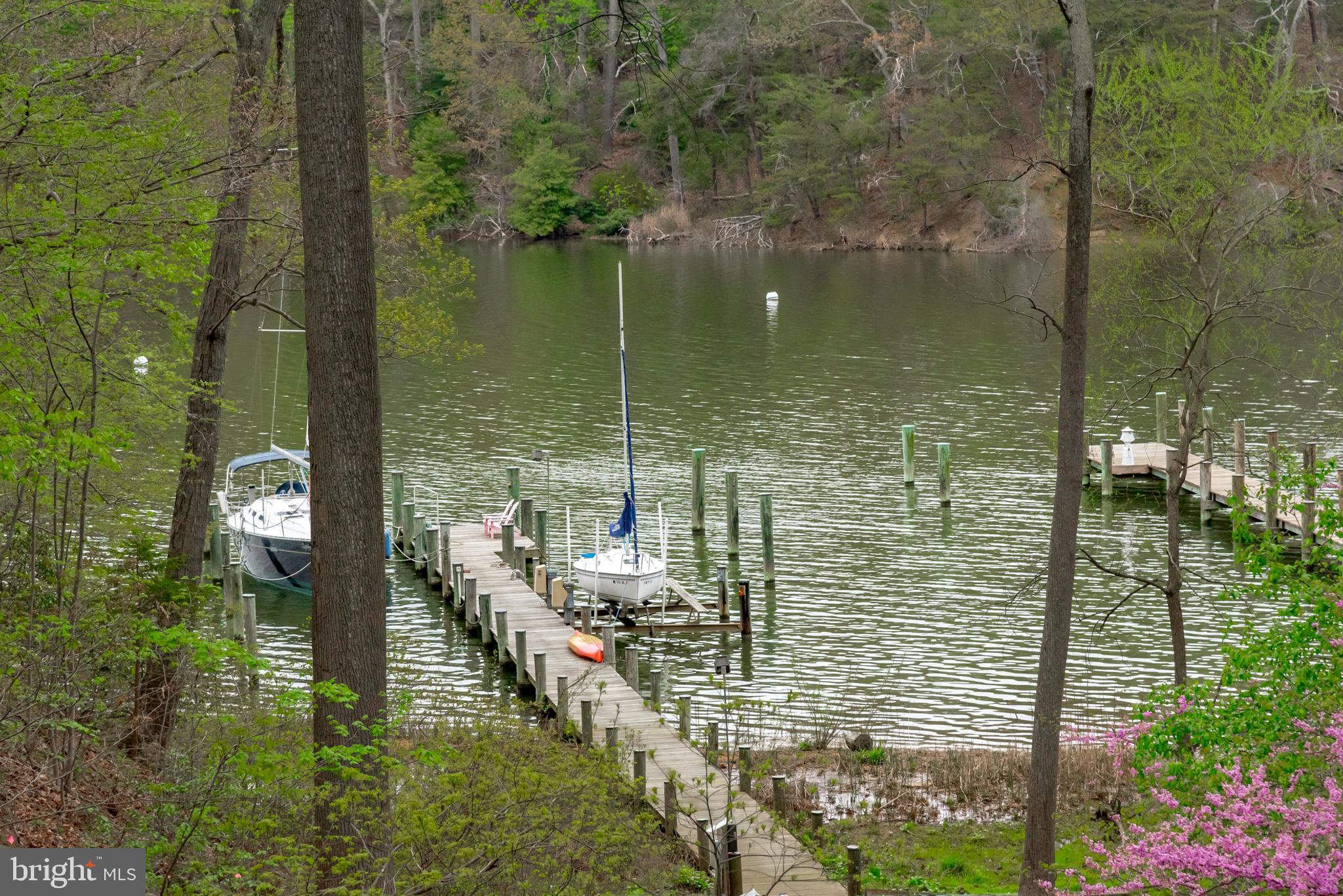 Custom built waterfront home located on Luce Creek offers a serene setting on 2 acres with private, protected deep water pier.  A deep, brick, covered front porch welcomes visitors setting the tone for this classic, home with over 5800 sq feet of finished space.  Inside, warmth and character radiate from the family room, breakfast nook, and gourmet updated kitchen located across one side of the house. The rooms are generous in size and proportional. The high ceilings add volume and architectural interest. The first-floor primary suite is private and spacious with two walk-in closets and renovated custom bathroom.  Three gas fireplaces, distinctive moldings, hardwood floors insure timeless elegance. The home office/solarium with private entrance is located between the main house and the garage for easy access. Upstairs, three additional bedrooms and a loft comprise over 1,000 square feet of living space There is an additional private office or bonus room for extra living space above the garage. The walk out lower level has a spacious recreation room/exercise space/5th bedroom and full bath as well as a large workshop. Outdoor space is perfect for entertaining and relaxation with a screened porch, stone patio and easy maintenance deck and hot tub. Rare opportunity to access the deep-water pier via shared driveway allows for easy provisioning of your boat for outings on the Chesapeake Bay.  Conveniently located in the community of River Watch minutes from the hip restaurants of West Annapolis and easy access to Route 50.
