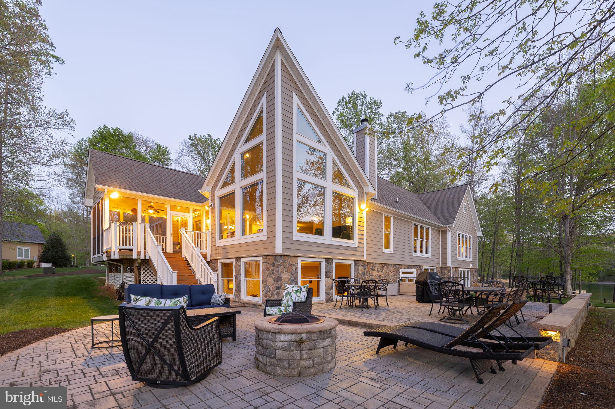 Tucked away on the private side of Lake Anna in the highly desirable Noah's Landing community, this custom-built waterfront retreat offers the perfect blend of privacy, quality craftsmanship, and unforgettable days on the water. Set on a beautifully wooded 1-acre lot with 230 feet of riprapped shoreline, deep water, and peaceful lake views, this property captures everything people love about lake living, offering the feel of a true lake house and a genuine escape from the pace of everyday life. High-speed Firefly fiber internet is available. Inside, you'll find a thoughtfully designed home filled with quality finishes and timeless style. The great room welcomes you with soaring vaulted ceilings, expansive floor-to-ceiling windows that frame the lake, and a stunning floor-to-ceiling stone wood-burning fireplace that creates a warm and inviting gathering space. Hunter Douglas remote-controlled blinds add convenience and comfort. The spacious kitchen was designed with entertaining in mind and features stainless steel appliances, granite countertops, soft-close cabinetry, a center island, breakfast bar seating, and a walk-in pantry. Just off the kitchen, a stylish wet bar with Silestone countertops makes hosting family and friends effortless. Engineered hardwood flooring, 9-foot ceilings, and an open-concept layout create a bright, airy feel throughout the home. Offering 5 bedrooms and 3.5 baths, there's plenty of room for family, guests, or rental potential. The lakeside main-level primary suite is a true retreat, featuring beautiful water views, dual walk-in closets, separate vanities, and a tiled walk-in shower with dual niches. The lower level offers a spacious family room, three additional bedrooms, and two full baths, including one with a private ensuite that provides added comfort and privacy for guests. Plantation blinds in two of the bedrooms add a relaxed coastal touch that perfectly complements the lake lifestyle. Step outside and you'll discover where this property truly shines. The screened-in porch offers a comfortable place to enjoy the lake views, morning coffee, or quiet evenings without giving up the fresh air. The expansive paver patio creates multiple outdoor living spaces for dining, relaxing, and gathering around the fire pit after a day on the water. A dedicated propane line for the grill makes cookouts easy, while a gentle path leads to your private boathouse featuring an electric boat lift, storage room, and a large sun deck positioned over deep water and perfect for soaking up the sun, swimming, fishing, or watching boats cruise by. Additional features include a whole-house generator, lake-fed irrigation system, HardiPlank and stone exterior, a Rinnai tankless water heater, and an attached garage. TVs, washer and dryer, garage freezer, and the additional refrigerator in the storage room all convey. This home makes the perfect full-time waterfront residence, a weekend getaway, or an investment opportunity with strong rental potential. From morning coffee overlooking the water to sunset boat rides and evenings around the fire pit, this is the kind of lake home where lasting memories are made and every day feels like a vacation.
