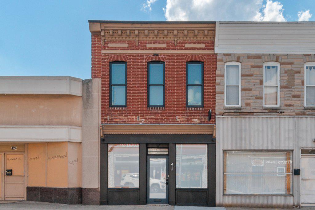 Pristine live/work gallery and residence in Baltimore’s Highlandtown Arts District, formerly known as Springsteen Gallery. This turnkey mixed-use property offers over 2,600 square feet of thoughtfully designed commercial and residential space and will appeal to the most discerning of buyers. The property benefitted from two extensive renovation phases — first transforming the gallery and commercial areas, followed by a comprehensive redesign of the residence above — resulting in a seamless blend of contemporary living, professional functionality, and architectural detail.

The striking façade has been carefully restored with renovated brickwork, updated doors and windows, and a restored second-floor center window that complements the replacement of the three front-facing upper windows. Additional exterior improvements include a new roof and gutters, installed in 2021, along with outdoor security cameras, a secure exterior hydrant, and a clean rear alley for convenient access.

The commercial/gallery level was designed with flexibility, safety, and professionalism in mind. In 2021, the commercial and residential portions of the property were separated with two-hour fire-rated walls, ceilings, and doors. The gallery space features skylights, gallery lighting, recessed lighting, safety exit signage, and exceptional natural light throughout. Additional first-floor amenities include a private office, security room, utility closet with stainless steel utility sink, half bath, and a handicap-compliant bathroom. The building is also equipped with three separate BGE meters serving the commercial, residential, and egress/common areas independently.

The fully renovated upper-level residence showcases sophisticated modern finishes and carefully curated design elements throughout. The designer kitchen features engineered white oak flooring by ADM Flooring, custom Ikea cabinetry and countertops, a Grohe faucet, Kraus sink, Bosch appliances, and a gas-powered range with hood. An oversized island provides seating and entertaining space, while room for a dining table adds functionality and warmth.

The elevated living area is filled with natural light from skylights, transom windows, and oversized windows with custom flower boxes. Architectural details include custom stairs with an oak slat wall and railing system, frameless custom interior doors with steel frames, premium chrome hardware, and European hinges.

The spa-inspired bathroom was meticulously renovated with terrazzo tile flooring, Zia ceramic wall tile, a flush-installed Wetstyle shower pan, Kurdi Schluter waterproofing system, Laufen x Kartell vanity, and premium designer fixtures, including Grohe and Duravit elements. The spacious bedroom includes a walk-in closet, ceiling fan, and blinds, while recessed lighting extends throughout the residence. A premium ceiling fan with motion and humidity detection adds additional comfort and efficiency.

Mechanical upgrades completed in 2025–2026 include a high-efficiency heat pump providing heating and cooling throughout the building and a gas-powered Bosch tankless water heater. The partial basement offers additional utility and storage with rubber mat flooring and storage racks, while the crawl space includes installed vapor barriers for added protection and efficiency.

A rare opportunity to own a truly turnkey mixed-use property combining refined residential living with professionally designed gallery and workspace in one of Baltimore’s most vibrant arts communities.