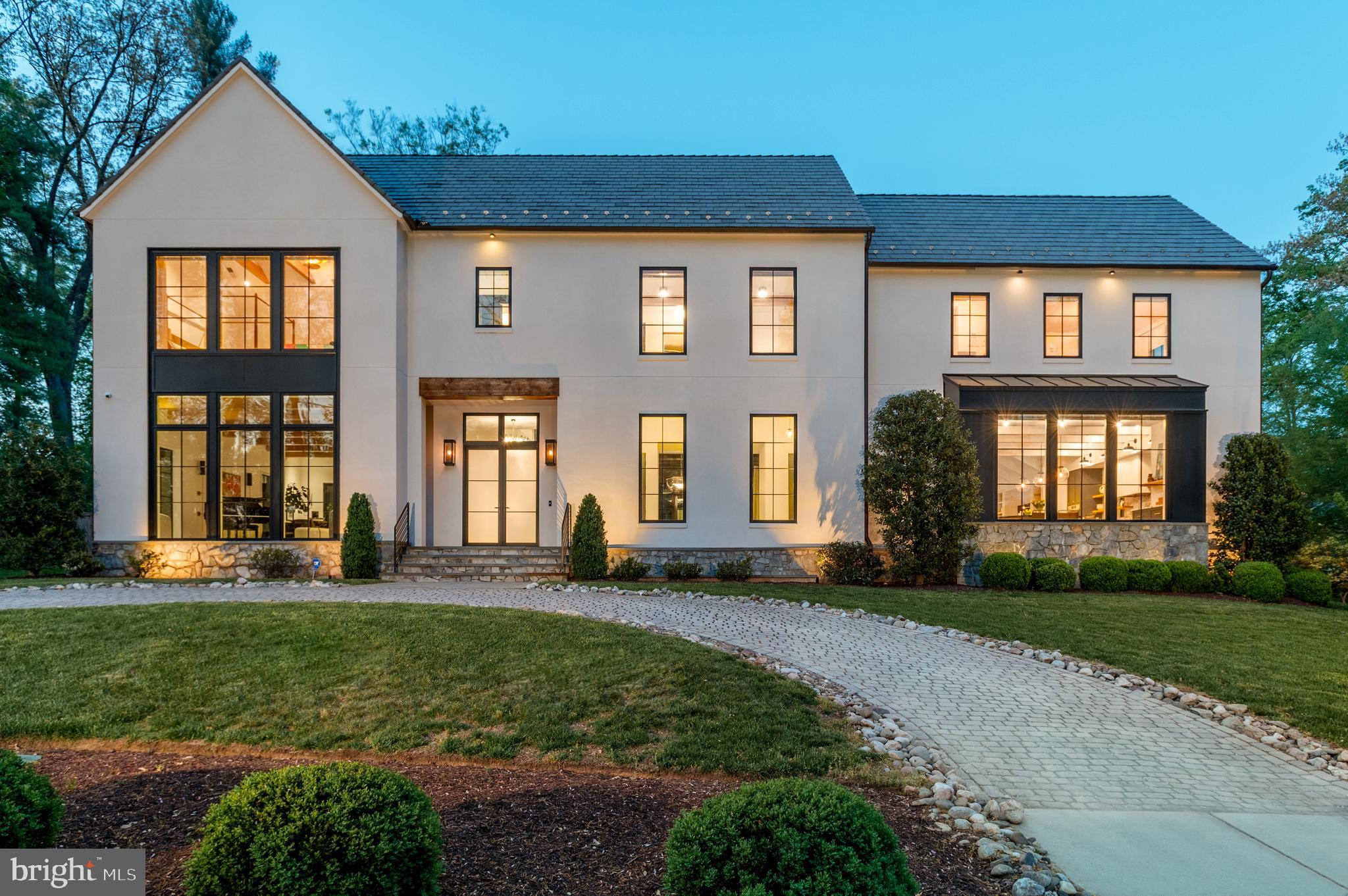 Set on a prominent .75-acre corner lot, 7101 Longwood Drive is a masterfully executed custom residence with design-forward panache. Built in 2018 by GBI Builders, designed in collaboration with architect Carmel Greer and interior designer Julie Geyer, this stunning home spans 9,100 square feet across four meticulously finished levels. The home unfolds with a sense of scale (note the 11’ ceilings on main level), light, and intention at every turn with high-end designer finishes including stunning custom lighting. Outdoors, the home transforms into a private resort surrounded by mature trees and landscaping for added privacy with a stunning heated in-ground pool, expansive patio, and outdoor kitchen. A grand, light-filled foyer makes an unforgettable first impression with a Murano glass chandelier and anchored by a sweeping, sculptural staircase with refined detailing that rises dramatically through the home. Wide-plank white oak hardwood floors, elegant millwork, and soaring ceilings carry throughout, setting a cohesive tone of understated luxury. Formal living and dining rooms are both gracious and inviting—ideal for entertaining—while the dining room connects seamlessly to the kitchen via a fully outfitted butler’s pantry, complete with custom cabinetry and additional prep space. The formal living room is anchored with a fireplace, white oak wood in ceiling beams, and doors leading to the covered patio with retractable screens. The kitchen is a true centerpiece: an expansive, chef-caliber space with Calacatta Vagli counters and backsplash, an oversized island, high-end appliances (including a Dacor range and fridge/freezer), custom cabinetry, Brizo fixtures, and designer lighting. A sun-drenched breakfast nook, wrapped in windows and additional built-in cabinetry. The kitchen flows effortlessly into the family room, where a statement fireplace and coffered ceilings create a warm yet elevated gathering space. Large glass doors blur the line between indoors and out. A private office with bespoke built-ins offers a quiet retreat, while a thoughtfully designed mudroom with ample storage connects directly to the three-car garage. Finishing this level are two powder bathrooms. Upstairs, the primary suite is both serene and sophisticated, featuring white oak wood in ceiling beams, custom automated window treatments, dual custom walk-in closets, and a spa-like bath clad in luxurious finishes —complete with Nero Marquina marble counter and floors, a freestanding soaking tub, oversized glass-enclosed carrara shower and walls, waterworks hardware, and dual vanities. Three additional bedrooms are beautifully appointed, accompanied by two well-designed baths and a versatile lounge space ideal for relaxing or studying. The top level provides an additional private suite. The lower level is designed for indulgent living and entertaining, featuring a sprawling recreation space, a showstopping wine cellar—with a biometric lock, standalone cooling system, extensive storage and space for a tasting table—serves as both a functional and visual focal point. This level also includes a fitness room, an additional bedroom and full bath, and storage. The professionally landscaped exterior serves as an extension of the home and is the perfect place to enjoy the upcoming summer months. A beautifully designed patio anchors the backyard, featuring a covered living area with retractable screens, heaters, a fan, and a fireplace. The outdoor kitchen is fully equipped  with Granite countertops, a mini-fridge, built-in grill and gas burner, warming drawer, and ice maker for effortless entertaining, while the pool—set against lush landscaping—creates a striking and tranquil backdrop. A circular driveway enhances the home’s stately curb appeal, complemented by a secondary driveway leading to the side-entry three-car garage.