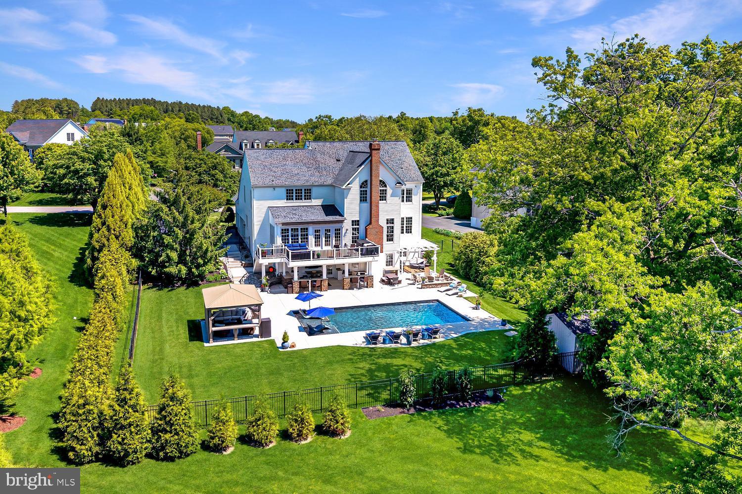 This exceptional brick-front Colonial estate blends timeless elegance with resort-style living, creating an extraordinary retreat where luxury, comfort, and unforgettable entertaining come together seamlessly. Perfectly positioned on a beautifully landscaped 0.46-acre tree-lined homesite, the property offers remarkable privacy while delivering an incredible indoor and outdoor lifestyle. Featuring six bedrooms, five and a half bathrooms, and four finished levels, every space has been thoughtfully designed for both grand entertaining and everyday living.
<br><br>
The curb appeal is undeniable from the moment you arrive, with mature landscaping, manicured gardens, and a stately three-car side-load garage creating a memorable first impression. Beyond the front entry, the backyard transforms into a private outdoor sanctuary designed to feel like a luxury vacation destination. The sparkling pool serves as the centerpiece, surrounded by an expansive sundeck perfect for lounging in the sun. A charming gazebo provides a shaded retreat, while a custom firepit area framed by retaining walls creates the ideal gathering place on cool evenings. Separate grilling and entertaining areas offer endless opportunities for hosting family and friends. The upper-level deck with retractable awning overlooks the beautiful setting below, while the expansive lower patio creates yet another destination for relaxation with granite-topped gathering bars, extensive seating areas, outdoor refrigeration, icemakers, and room for celebrations large and small.
<br><br>
Inside, a dramatic foyer makes a stunning first impression, framed by formal living and dining rooms and enhanced by elegant trim work, detailed moldings, and a sweeping staircase. A private home office with custom built-ins provides the perfect work-from-home environment.
<br><br>
The kitchen serves as the heart of the home and was designed with both beauty and function in mind. Stunning quartz countertops, premium appliances, abundant prep space, and an exceptional walk-in pantry with custom built-ins and tailored organization create a space that is as practical as it is impressive. The adjoining morning room fills with natural light and provides direct access to the rear deck, while the spacious family room is anchored by an impressive stone fireplace.
<br><br>
Upstairs, the luxurious primary suite serves as a private retreat featuring cathedral ceilings, a spa-like bath with soaking tub, dual vanities, and an oversized frameless glass shower. Two expansive walk-in closets with custom built-ins and a dedicated dressing area complete the suite.
<br><br>
The secondary bedrooms are equally well appointed, with one offering a private ensuite bath while two additional bedrooms share a spacious hall bath. An upper-level laundry room adds everyday convenience. The finished attic level offers exceptional flexibility with a bedroom and full bath, creating the perfect teen retreat, guest suite, or private lounge space.
<br><br>
The fully finished lower level elevates the home's entertainment experience even further. A custom built-in bar features a kegerator, beverage refrigerator, dishwasher, and icemaker, creating an impressive hospitality space. A dedicated movie room with projector and screen provides an authentic theater experience, while a spacious game room and exercise room add versatility. The lower level also includes a private bedroom with attached full bath and a second laundry room, making it ideal for guests or extended stays.
<br><br>
Additional major updates provide peace of mind, including a roof replaced with top-of-the-line 50-year wind-resistant shingles, along with recently replaced HVAC systems and water heater.
<br><br>
Perfectly positioned just 0.9 miles from the Metro with immediate access to the Toll Road and moments from Dulles International Airport, this remarkable residence delivers luxury living and exceptional convenience for commuting, travel, and everyday life.