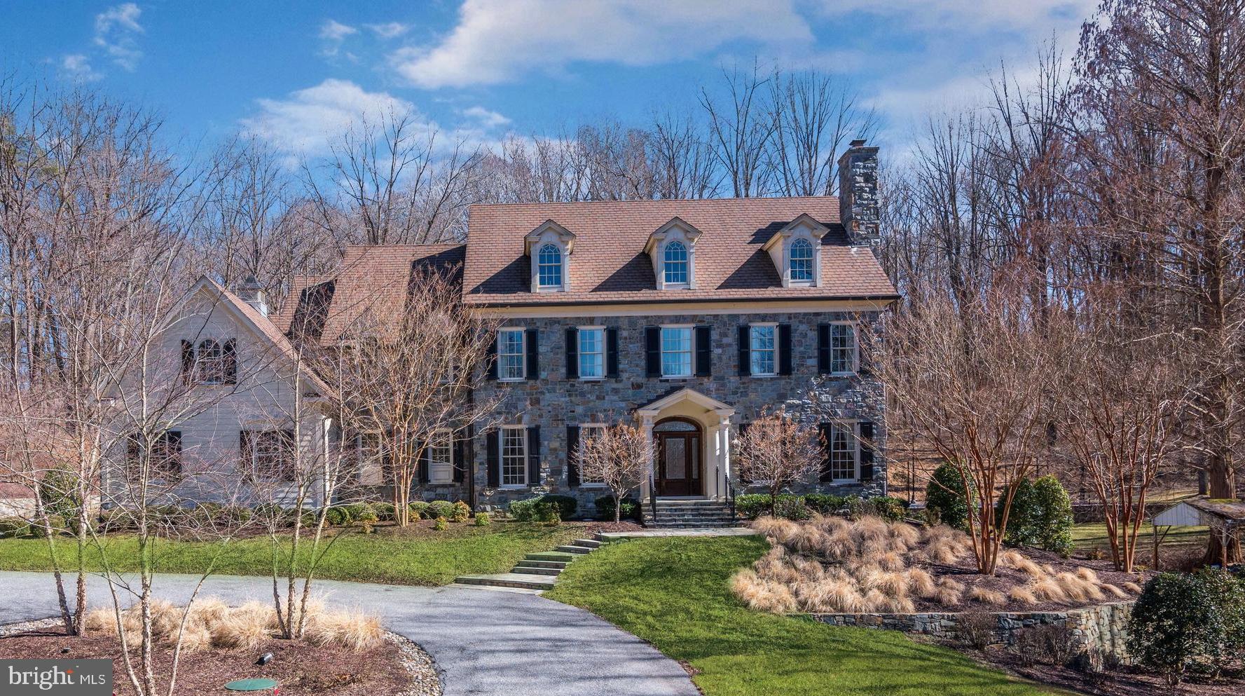 Custom built with exceptional detail and perfection, this Ted Visnic architectural masterpiece (Pennsylvania Farmhouse) is one of a kind, showcasing locally quarried carderock stone. This beautiful stone was used in the design as a unifying element on exterior features including the entry pillars, retaining garden walls, front elevation, and twin chimneys. Enchantment begins with a private drive flanked by stone pillars and black, board-fencing that together frame the majestic view of this home on the hill. Arrival is celebrated by a circular drive and landscape lighting, followed by a welcoming portico, paired columns, and stone porch.  The entry door is solid wood with a leaded glass transom, sidelights, and a sweeping arched vestibule-styled trim.   Inside, a stunning open foyer is sided by sweeping arches and trim that remember the entry portico, whilst unfolding graciously into an extended foyer, rear portico, and a grand winding stair.  Raised, solid wood panel wainscoting set at forty-two inches above the exotic walnut wood floor is a stunning combination and hallmark feature. Living and dining formals flank the foyer, boasting windows that frame a gas fireplace in the living room and a banquet-sized dining room equipped with an adjacent butlers service pantry, wet bar, and wine chiller. The grand center hall terminates with light streaming in through an atrium door and a lanai overlooking the dining patio, landscaping, footbridge, play equipment, and sport court. Sharing the light stream and view is the formal study with French doors, two walls of library built-ins, a media wall, and a gas fireplace with an oversized mantel.   Gatherings large and small will gravitate to the gourmet kitchen and oversized entertainerâ  s island and breakfast bar embellished with pendants above, granite top, and furniture-style turned legs. Custom-designed wood cabinetry on the island is contrasted with the light painted cabinets and a decorative tile splash that wrap the perimeter. Professional appliances include a Sub-Zero fridge and a full-sized Sub-Zero freezer, a six-burner gas range, double oven, and a range hood with, and custom over-mantel millwork.   As the heart of the home, the kitchen is central to the adjacent breakfast room, family room, mudroom, homework station, and secondary back stair. In the family room, a floor to ceiling stone fireplace is flanked by built-ins that serve to anchor two walls of windows, and the striking wood floors to the deeply coffered ceilings above.  The seamless main level open plan is completed by two half baths.  Downstairs, there is something for everyone of every age, offering indoor fun for every season.  Currently used as an exercise room, a walk-out en-suite bedroom and full bath spaces are privately situated with full daylight windows and an atrium door to the lower patio. Flexible recreation spaces are perfect for gaming and foozball, while a pair of double doors invite entertaining and leisure with a game table area, billiards area, and a custom concrete bar surrounded by multiple media options. Friends and family will especially enjoy the theater room complete with reclining leather seats, risers, projector, and large screen, just like at the movies!     Upstairs, a back secondary stair rises up to access five en-suite bedrooms, including a lavish Ownerâ  s suite and sitting room with three walk-in closets, custom organizers, and a sumptuous partners luxury bath.  A central, oversized shower with body sprays and spa-like jetted tub is flanked by separate vanities and two private water closets. Accommodations continue to a fully finished fourth level bedroom suite with gable windows and an attached full bath. Additional features include a Control4 home automation system, energy-efficient geothermal heating and cooling, and a whole home generator (60kv) tied to 1, 000 gallons of propane. Come home to perfected living near 10 schools in between DC and Baltimore!