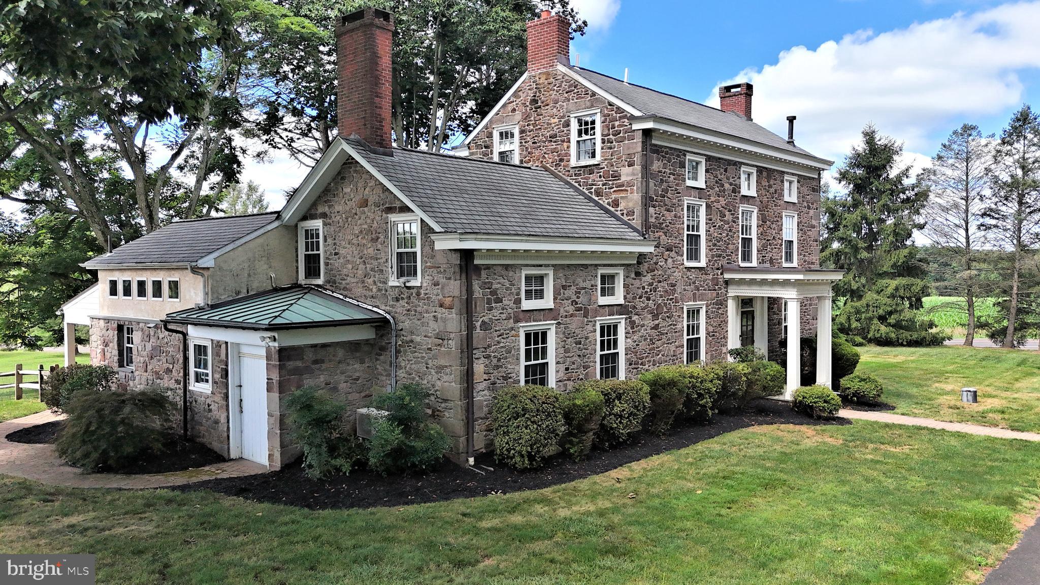 Steeped in Bucks County history and thoughtfully adapted for modern living, Hope Farm presents a rare opportunity to own a landmark residence listed on the Bucks County Register of Historic Places. This is an honorific listing as there are no restrictions on the home for changes.  Few properties offer such a complete estate experience, where historic structures, exceptional recreational amenities, and thoughtfully designed outdoor spaces combine to create a true family compound in the heart of Bucks County. Originally constructed circa 1790 and expanded during the Greek Revival period of the mid-19th century, this distinguished three-story Stone Manor Farmhouse has been carefully preserved to honor its heritage while embracing the comforts expected by today's homeowner. Situated on 1.54 acres and abutting 8 acres of protected open space, the property enjoys picturesque views and a sense of privacy rarely found. Throughout the residence, the craftsmanship of a bygone era is showcased through original wide-plank pine floors, handcrafted millwork, exposed stone accents, period fireplaces, dual staircases, and charming architectural details spanning all three finished levels. Historic character blends seamlessly with thoughtful updates, creating living spaces that are both timeless and welcoming.
At the heart of the home is a beautifully appointed country kitchen , thoughtfully designed for gathering and entertaining. Custom Lancaster County pine cabinetry, a suite of professional-grade appliances, radiant heated flooring, and generous workspace create a setting equally suited for holiday celebrations and everyday living. Multiple living and sitting rooms offer flexibility for entertaining guests, relaxing with family, or creating dedicated work from home spaces. The upper two levels feature 4  bedrooms, 2 beautifully renovated full baths completed in 2021 and 2022,  convenient second-floor laundry room, and an adjoining office area. The rear covered porch overlooks the beautiful open space. The full unfinished basement has a concrete floor and provides abundant storage and utility space. Beyond the residence, the grounds reveal a collection of remarkable structures and amenities rarely found together on a single property. A historic stone icehouse with bluestone flooring offers a fascinating connection to the property's past and features a fireplace with wood-burning insert, along with a lower-level storage area (ideal for wine storage?). Outdoor entertaining takes center stage at the Entertainment Barn, a favorite gathering space featuring a stone bar, televisions, and heating for extended seasonal enjoyment. Whether hosting intimate family gatherings or larger celebrations, this versatile venue creates an inviting atmosphere throughout much of the year. Recreational opportunities abound across the property. A full-size basketball court, a horseshoe pit, fire pit, expansive lawn areas, and a dedicated children's play area complete with swings, playhouse, climbing wall, and treehouse provide endless opportunities for enjoyment. Warm summer days are best enjoyed beside the custom heated in-ground pool and spa. The pool area is enhanced by a spacious pergola, expansive paver patio, and maintenance-free Jerith aluminum fencing.  A charming poolside changing room and historic functioning outhouse (the “PiPi Room”) add both convenience and character. The substantial Lancaster Amish-crafted barn, reconstructed in 2013, features five bays, including one with a second level, offering exceptional flexibility for vehicle storage, hobbies, workshops, collections, or equipment. The expansive driveway provides generous parking (25+ cars) capacity for guests and would perfectly suit contractors or landscapers needing space for their equipment. Combining historical significance, modern convenience, and exceptional spaces for entertaining, Hope Farm is more than a home-it's a destination!  ***Professional Photography July  10th ***