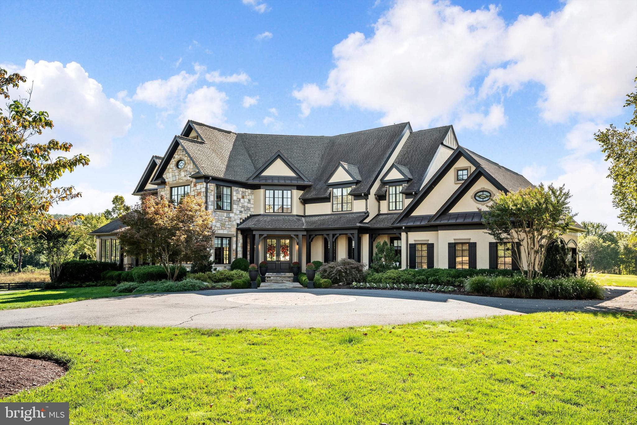 Welcome to a golfer’s dream retreat, set on a pristine one-acre homesite with commanding views of holes 9, 14, and 15 of the Jack Nicklaus Signature Golf Course. This luxurious residence, a former model home known as the "Nicklaus House," has been meticulously upgraded throughout, offering the ultimate in elegance, functionality, and modern design.
As you step into the grand foyer, you are greeted by a sweeping curved staircase and a new elegant chandelier. The main level showcases a formal dining room, a refined parlor, a private office with custom shelving, and a second office space for added versatility. The gourmet kitchen serves as the heart of the home, featuring a large center island with new quartz counters and backsplash, Sub-Zero and Wolf appliances, custom pantry with a barn door, and designer lighting throughout—perfect for both everyday living and stylish entertaining. The great room rises two stories high, with expansive windows and a stunning new quartz hearth and gas fireplace anchoring the space, while the adjoining family room offers a double-sided fireplace shared with the kitchen.
The three-car side-load garage has been outfitted with custom flooring, cabinetry, lockers, shelving, and three electric overhead storage lifts—perfect for organization and functionality.
The primary suite is a true sanctuary, boasting dual oversized walk-in closets, a new gas fireplace, and a spa-inspired bath with upgraded vanities and lighting. Each of the three additional bedrooms includes its own en-suite bathroom, all recently refreshed with new lighting and fixtures.
The finished basement is a showcase of craftsmanship, featuring a custom temperature-controlled wine cellar, a stylish family room with wood-beamed ceilings, and a full bar equipped with hidden storage, a two-drawer fridge, dishwasher, microwave, and ice machine. A new state-of-the-art golf simulator brings the fairway home, while a private bonus room with walk-in closet and spa-quality bath provides the perfect guest or au pair suite. Additional storage and a separate bathroom complete this exceptional level.
Every inch of this home has been thoughtfully upgraded to deliver the perfect blend of luxury, comfort, and functionality—all set within the exclusive, gated community of Creighton Farms. With sweeping golf course views and world-class amenities just outside your door, this property truly defines resort-style living.
