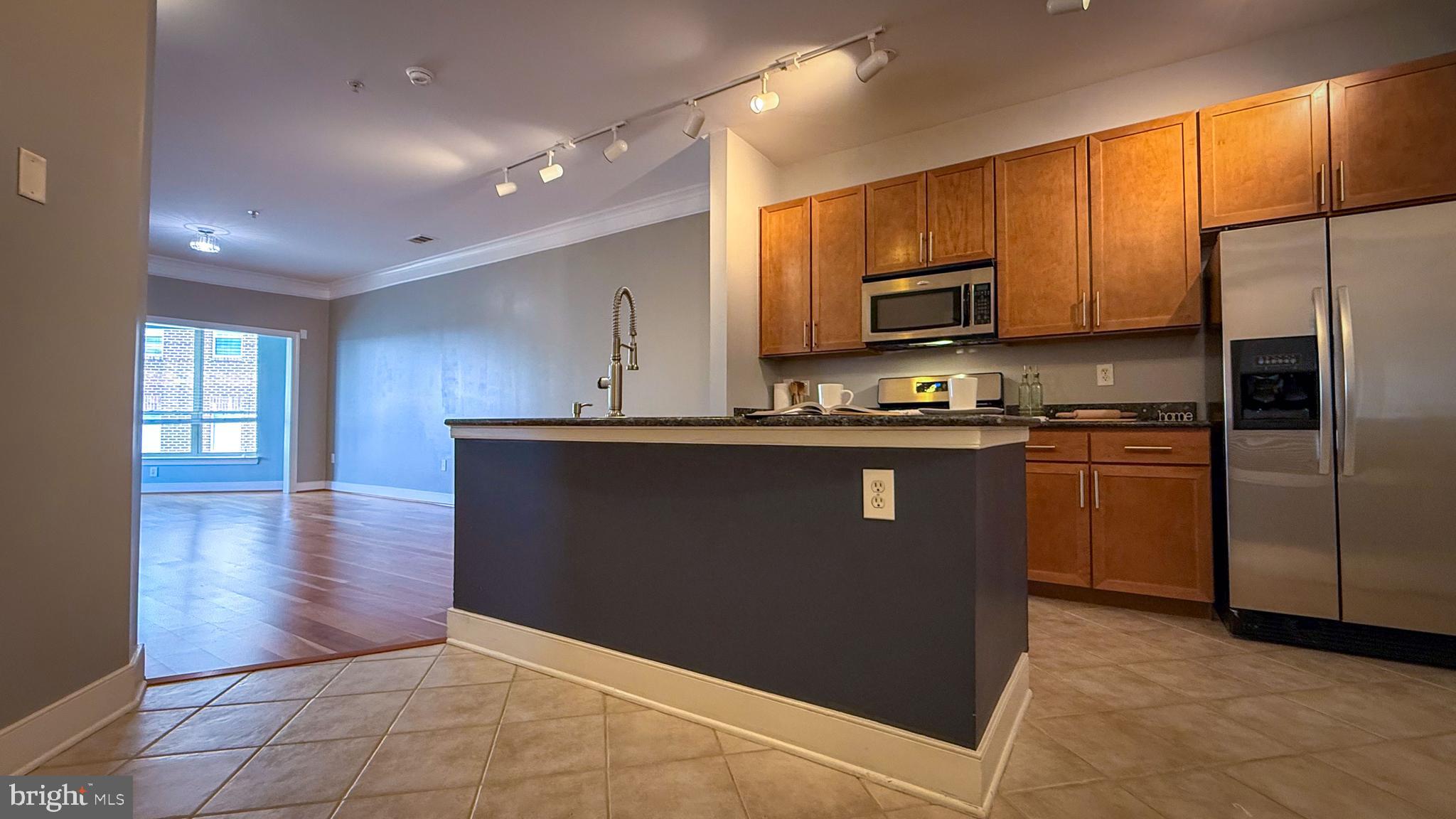 Experience luxury living at its finest in this rarely available 1-bedroom, 1 full and 1 half bath condo offering nearly 1,100 square feet of beautifully designed living space — comparable in size to many two-bedroom units. Neutral-toned walls create a warm and inviting atmosphere from the moment you enter. The spacious kitchen features stainless steel appliances, granite countertops, a large island with sink and commercial-style gooseneck faucet, plus a pantry for added storage. A built-in desk provides the perfect work-from-home setup, while the in-unit stackable washer and dryer add everyday convenience.

The thoughtfully designed half bath is ideal for guests, allowing privacy for the primary suite. Elegant wood flooring and double crown molding enhance the expansive living and dining areas. The bright solarium/den is lined with windows, filling the space with natural light. French doors offer a second entrance into the spacious primary bedroom, complete with an en-suite bath featuring a double vanity, separate soaking tub and shower, and a walk-in closet.

Enjoy resort-style amenities without leaving home, including a recently renovated fitness center, yoga room, billiards room, business center, outdoor pool, and a stylish resident lounge with kitchen and outdoor entertaining space. Conveniently located in Tribeca at Camp Springs, just minutes from Branch Avenue Metro Station, Restaurant Row, Joint Base Andrews, National Harbor, MGM, and Tanger Outlets.