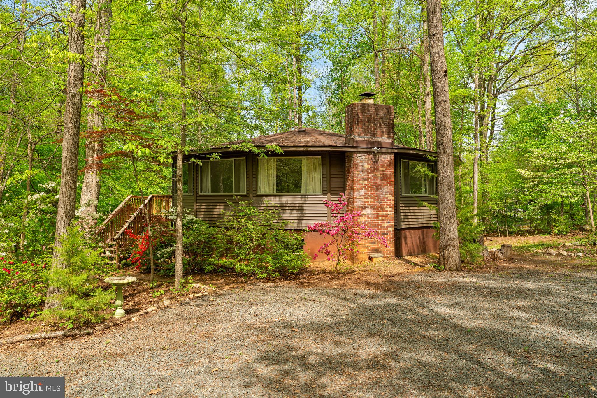 Escape to Lake of the Woods! This lovely round home sits on a wooded corner lot, steps away from Edgemont Beach. The main level of the home features a light-filled and open living room, with a table space.  The kitchen is right off the living room, with stainless appliances and a bar.  Enjoy the outdoors on the large deck, just off the kitchen and living room.  A full hall bathroom is on this level, along with the primary bedroom, with a walk-in closet and en suite bathroom, and a second large bedroom.  A spiral staircase leads to the mostly finished lower-level, which includes the rec room (with a wood burning fireplace), 3rd bedroom, full bathroom, laundry room (with utility sink & second fridge), a storage/utility room, and walk-out exterior doors.  Many updates have been to the home, and some of note include the roof & roof structure (2015), exterior vinyl siding (2025), bedroom carpet (2026), heat pump condenser motor (2020), living room windows and sliding door, other flooring, and more!  The wooded lot has two driveway entrances, ample parking, a picnic area, and a shed below the deck. The gated Lake of the Woods community offers an endless list of amenities, including two lakes, trails, parks, pools, beaches, sporting courts, a golf course, clubhouse, restaurant, equestrian center, fire & rescue department, and more! Don’t miss your opportunity to be the next owner of this one-of-kind property!