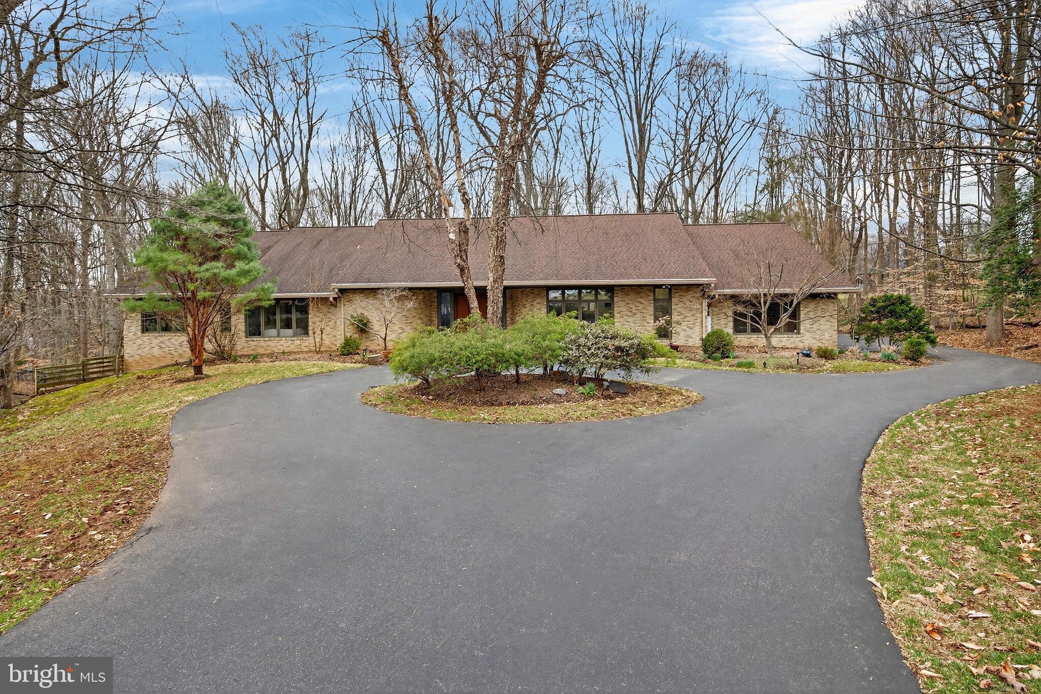 Tucked at the end of a quiet cul-de-sac on two wooded acres, the setting feels private and removed. Still, you’re only minutes from Potomac Village and Swains Lock on the C&O Canal.

The interior opens up immediately. Vaulted ceilings, good natural light, and a layout that flows without feeling forced. With over 7,200 square feet of total structural space, main-level living is genuinely hard to find at this scale, and the floor plan delivers it without compromise.

The kitchen was redone with solid wood cabinetry, quartz countertops, and a center island that ends up being where everyone lands. It connects directly to the living area, where a floor-to-ceiling fireplace and custom built-ins give the room some weight. Don’t miss the doors off the back that open to an elevated deck with nothing but trees behind it.

The primary suite is private and well-appointed. New carpet, soaking tub, oversized shower, and two large walk-in closets with custom built-ins. There’s also a private deck off the suite if you want a little separation from the rest of the house.

The rest of the layout has real flexibility. It works well for multigenerational living, a dedicated home office, or guest space, without feeling carved up. Downstairs, the finished lower level adds substantial room for a rec area, media setup, or whatever you actually need, plus a storage room that’s hard to fill.

A few other things worth knowing: a four-car garage and circular driveway, Hunter Douglas window treatments throughout, new washer and dryer, new front entry door, built-in ironing board, oversized linen and coat closets, and a new grinder pump.

It’s a straightforward house in the best sense. Private setting, practical layout, and the kind of details that hold up over time.​​​​​​​​​​​​​​​​
