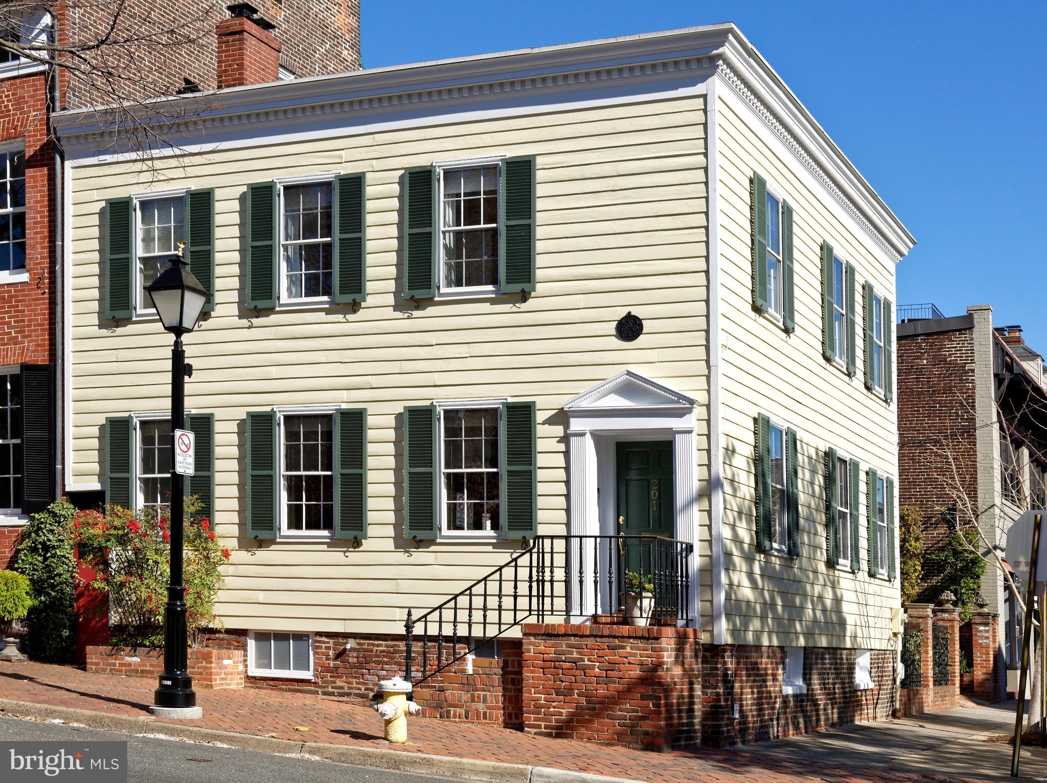 Built in 1860, this picture-perfect home with 3 bedrooms and 2.5 baths is brimming with style and elegance with views of the flowering gardens of the Carlyle House. This architectural gem sits on a prime corner lot complemented by historic exterior details including window shutters, dentil molding, front door pilasters, and a distinctive peak pediment which add character to the curb appeal. Beautiful hardwood floors, light-filled windows on the south and east, arched doorways, tasteful moldings, gas fireplace, and other fine elements reflect the classic charm of yesteryear with today’s modern conveniences.  
Inside awaits a welcoming ambiance embodied in the living and entertaining spaces.  The generously sized living room is 3 windows wide flooding the room with natural light.  A cozy gas fireplace and a stunning keystone archway are the focal points of the room, complemented by stylish built-in bookshelves and an open display niche.  This elegant space flows seamlessly into the formal dining room, with windows on the east, making it perfect for entertaining.  The bright and airy kitchen offers ample glass front cabinetry, recessed lighting, gas cooking, and access to the delightful terrace for outdoor enjoyment.  Completing the main level is a convenient powder room for guests, original staircase, and an ideal office space with direct access to the terrace. 
Upstairs sleeping quarters offer a peaceful retreat for relaxation.  The primary suite is divine with many windows, a bespoke wardrobe wall, and a large walk-in closet with custom shelving.  A luxurious 2023 renovated marble bath provides a pampered experience with a marble shower, designer fixtures, large vanity, heated towel rack, and brushed gold hardware. Two spacious guest rooms and a full bath provide comfortable accommodations or another office. The basement with natural light has sealed brick walls, an outdoor entrance with Bilco doors, a laundry area plus much storage.  A delightful patio area offers room for a table, a grill and many flowers.  One bricked off-street parking space adjoins the terrace.  Enjoy living in the heart of Old Town in a premier location just moments away from fine shops & restaurants, lush parks, and the picturesque waterfront.