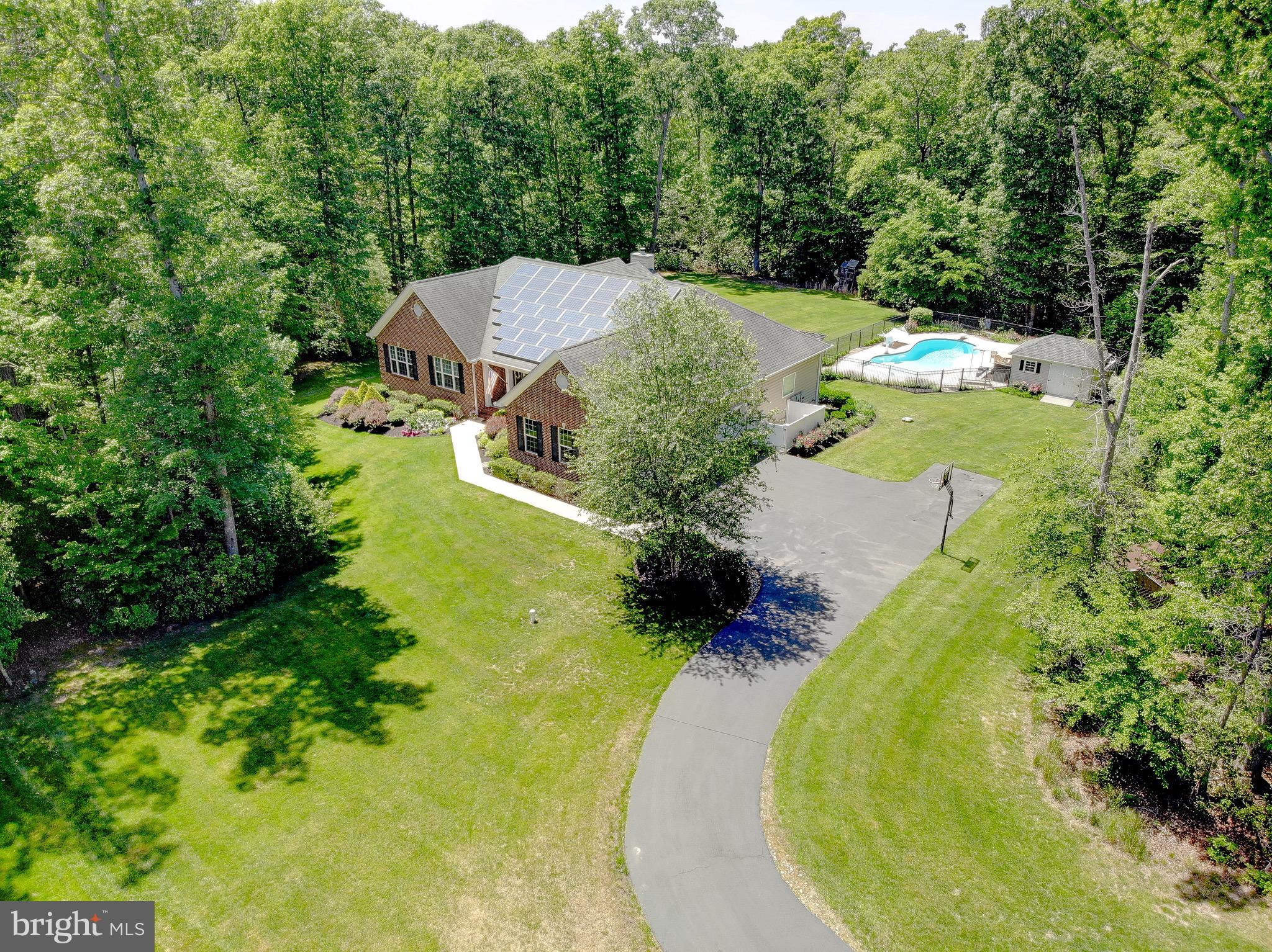 This well-maintained Winchester Model by Quality Built Homes offers approximately 6,300 square feet of finished living space on a 1-acre lot and reflects over $200,000 in upgrades and improvements. The brick rambler design includes a full basement, 6 bedrooms, 3.5 baths, and flexible spaces suited for a variety of living needs. The main level features 4 bedrooms and 2.5 baths, an open floor plan, hardwood flooring, crown molding, recessed lighting, and a spacious living area centered around a wood-burning fireplace with marble surround and mantel. The gourmet kitchen includes granite countertops, a center island, pantry, stainless steel appliances, convection wall oven, microwave, 30” gas cooktop, dishwasher, and refrigerator. Adjacent to the main living area is a 20’ x 20’ sunroom, providing additional space for everyday living or entertaining. Main-level laundry adds convenience. The primary suite includes a soaking tub, separate shower, double vanity, and walk-in closet. Three additional bedrooms are located on the main level. Outdoor amenities include an 18’ x 14’ Fiberon deck with vinyl rails, extensive hardscaping, brick paver patio with arbor, landscape lighting, underground irrigation system, and an in-ground heated pool with an 8.5-foot deep end, diving board, and shallow entry steps. The pool area is enclosed with black aluminum fencing. A pool shed with awning, wood shed, and basketball hoop convey. The finished lower level offers 9-foot ceilings, a large recreation room with bar area, 2 additional bedrooms, a full bath, exercise room, children’s play space, and generous storage. A 20’ x 20’ theatre/media room with projector screen and surround sound equipment provides additional recreation space. Additional features include a 3-car side-load garage with 9,000 lb vehicle lift, 17KW whole-house generator, water softener and treatment system, tankless water heater, attic fan, programmable thermostat, Ring doorbell, exterior cameras, energy-efficient windows, and propane heating. Conveniently located near top-rated schools with an accessible commute to Joint Base Andrews, Washington, D.C.!