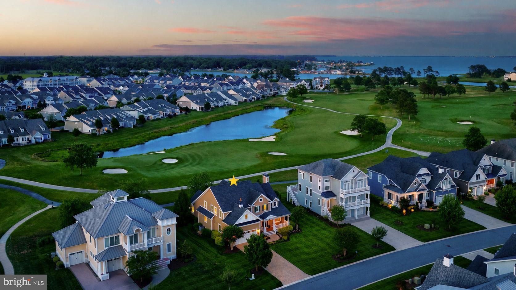 Welcome to 27551 Medallion Avenue, an exceptional golf and waterfront home in the prestigious gated community of The Peninsula on the Indian River Bay. A rare and highly sought-after offering, this property provides the next owner the opportunity to obtain immediate Reserve Membership, bypassing the typical golf membership waiting list. Perfectly positioned along the 10th fairway and green, with two ponds and sweeping views of the Indian River Bay, this meticulously maintained four-bedroom, two-and-a-half-bath residence offers refined finishes, quality improvements, and an exceptional resort lifestyle. Exceptional curb appeal begins with a beautiful paver driveway and front walk, professionally landscaped grounds, a lush, irrigated lawn, and timeless architectural details, including shake accents, horizontal and vertical siding, board-and-batten shutters, multiple roof peaks, a bronze pineapple weathervane, and a welcoming covered front porch enhanced with new TimberTech decking.  Inside, rich hardwood flooring extends throughout the main level, complemented by crisp white wainscoting, plantation shutters, beadboard accents, and elegant crown molding. Just off the foyer, a formal dining room offers the flexibility to serve as a private home office.  Designed for both everyday living and entertaining, the gourmet kitchen features granite countertops, a breakfast bar, new stainless steel GE Profile appliances (10/24), double wall ovens, a four-burner cooktop, a new Broan stainless steel range hood, display cabinetry, under-cabinet lighting, pull-out drawers, two pantries, and an appliance garage. The adjoining casual dining area opens to a screened porch with an Eze-Breeze enclosure and a beautifully designed two-tier paver patio with raised sitting walls and a pergola, creating inviting outdoor living spaces that overlook the golf course, ponds, and Indian River Bay.  Anchored by a cozy gas fireplace, the great room captures these extraordinary vistas through expansive windows, ensuring the home's remarkable setting remains the focal point throughout the day.  The first-floor primary suite offers a tray ceiling, elegant round transom window, two walk-in closets, and a luxurious en suite bath with dual granite vanities, a soaking tub, frameless glass walk-in shower, and a private water closet.  Upstairs, a spacious loft connects three additional bedrooms and a full hall bath. The large guest bedroom features two walk-in closets, including an oversized closet positioned above the powder room that offers the opportunity to create a third full bath, establishing a future second primary suite if desired. An adjoining bonus room provides excellent storage or flexible space for hobbies and seasonal items.  Ideally located just a five-minute stroll from the clubhouse and amenity center, residents enjoy access to The Peninsula's exceptional amenities, including the Jack Nicklaus Signature Golf Course, elegant clubhouse with dining, full-service spa, fitness center, indoor and outdoor pools, an adults-only heated pool, wave pool, sandy beach, tennis, pickleball, basketball, scenic walking and biking trails, and a vibrant social calendar. Conveniently located near historic Lewes, Rehoboth Beach, shopping, dining, and Delaware's award-winning beaches, this exceptional home offers the perfect blend of luxury, comfort, and coastal living.