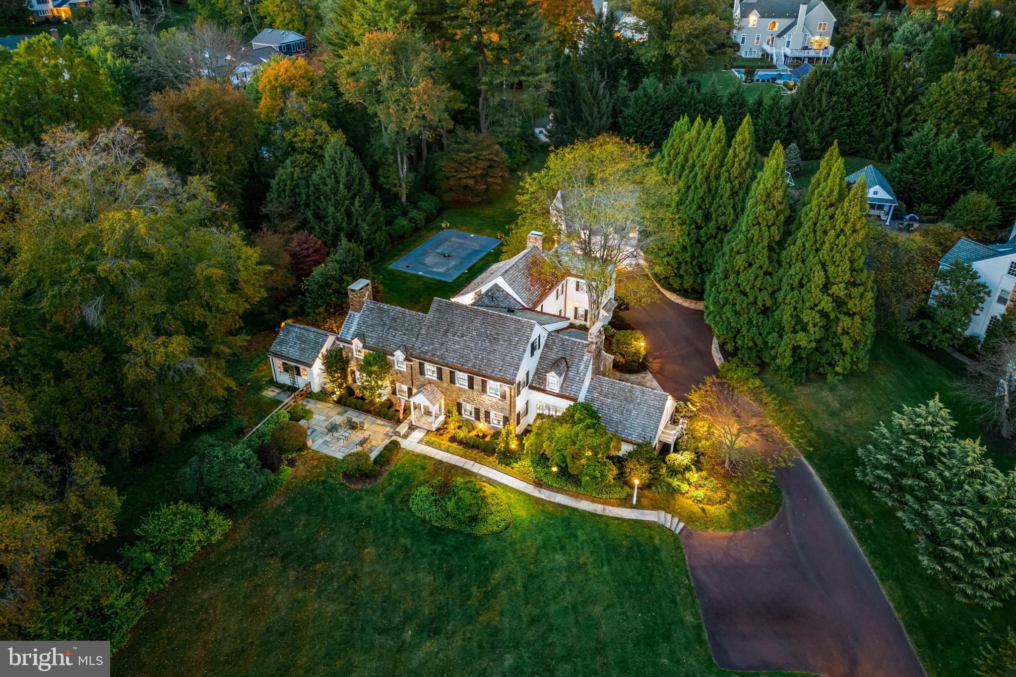 This property is 4 acres, 2 separately  deeded lots. The home sits on 2.5 acres and the lot next to it is 1.5 acres. Drive down one of Bryn Mawr’s most desirable tree-lined streets and turn into the long driveway lined with lamp poles and specimen plantings. The stately stone manor home with white siding, black shutters and slate patios front and rear say you’ve arrived. This fully updated classic Pennsylvania farmhouse sits on two fenced-in parcels totaling more than 4 acres in the heart of the Main Line, in the coveted Radnor School District. 
This 6000 + Okie farmhouse, a Colonial Revival main home, was built in 1942 and redesigned for modern living in 2014 by architect Ann Ledger of Wayne. It (main house)features 5 bedrooms, 5 full and 2 half baths on 2.5 levels, plus a finished lower-level bonus room and a 1-bedroom, 1 bath studio apartment/guest house  above the detached garage. Inside you’re surrounded by rich architectural features from past and present—from arched doorways, Dutch doors with rustic wrought-iron hardware, beautiful hardwood floors and 3 fireplaces, to built-in lockers in the mudroom and bookshelves in both offices, marble bathrooms with seamless shower doors and walk-in closets everywhere. Throughout, generous windows offer great views of the property from every angle and fill the home with light.
On the main level, the foyer opens to stairwells to the upper level and finished lower level and features a formal powder room. Both the living room and great room feature fireplaces. French doors in the living room open to a slate patio. The equally spacious great room has split doors to the back patio and the mudroom addition and opens to the kitchen and breakfast room as well. A family room provides additional informal gathering space and a 2nd stairwell to the upstairs hallway. Two offices—one off the kitchen and the other opening to the backyard—feature built-ins in beautiful shades. 
A butler’s pantry—fully equipped with a beverage refrigerator, dishwasher and icemaker—services both the dining room and the center-island kitchen—a chef’s delight with Thermador 6-burner stove with griddle and range hood Thermador double wall oven and warming drawer, a farmhouse sink and other high-end stainless steel appliances. Featuring white inset cabinets, a subway tile backsplash and white beadboard ceiling, this cheery space opens to a large breakfast room overlooking the patios and pool. There’s also a door to the driveway area for family members and “backdoor friends.”
On the first upper level, the primary bedroom features a large covered balcony with a gorgeous view of the pool and backyard, as well as two walk-in closets with built-in storage and a luxurious private bath with radiant-heated tile floors, double sinks and high vaulted ceilings—part of the 2014 addition. Three large additional bedrooms with en suite baths were also part of the renovation, and a laundry room with built-in cabinets and countertops adds convenience. On the second upper level, a large room and full bath could be used as a playroom or additional bedroom. On the lower level, a finished bonus room with fireplace provides flexible space to suit your family’s style.
The main-level mudroom has tile floors, an informal powder room and walk-in closet, along with built-in cubbies, and a bar with refrigerator to serve the pool area. Picture yourself sitting by the in-ground pool/spa listening to the soothing sound of the Kirk’s Run creek, which runs alongside the property. Off the pool area, a detached two-car garage includes a one-bedroom studio apartment with full bath and kitchenette for your guests’ convenience and your privacy.
Gorgeous inside and out, this classic residence offers the best of town and country living just three miles from both the Villanova and Bryn Mawr train stations and within walking distance of the prestigious Agnes Irwin School.