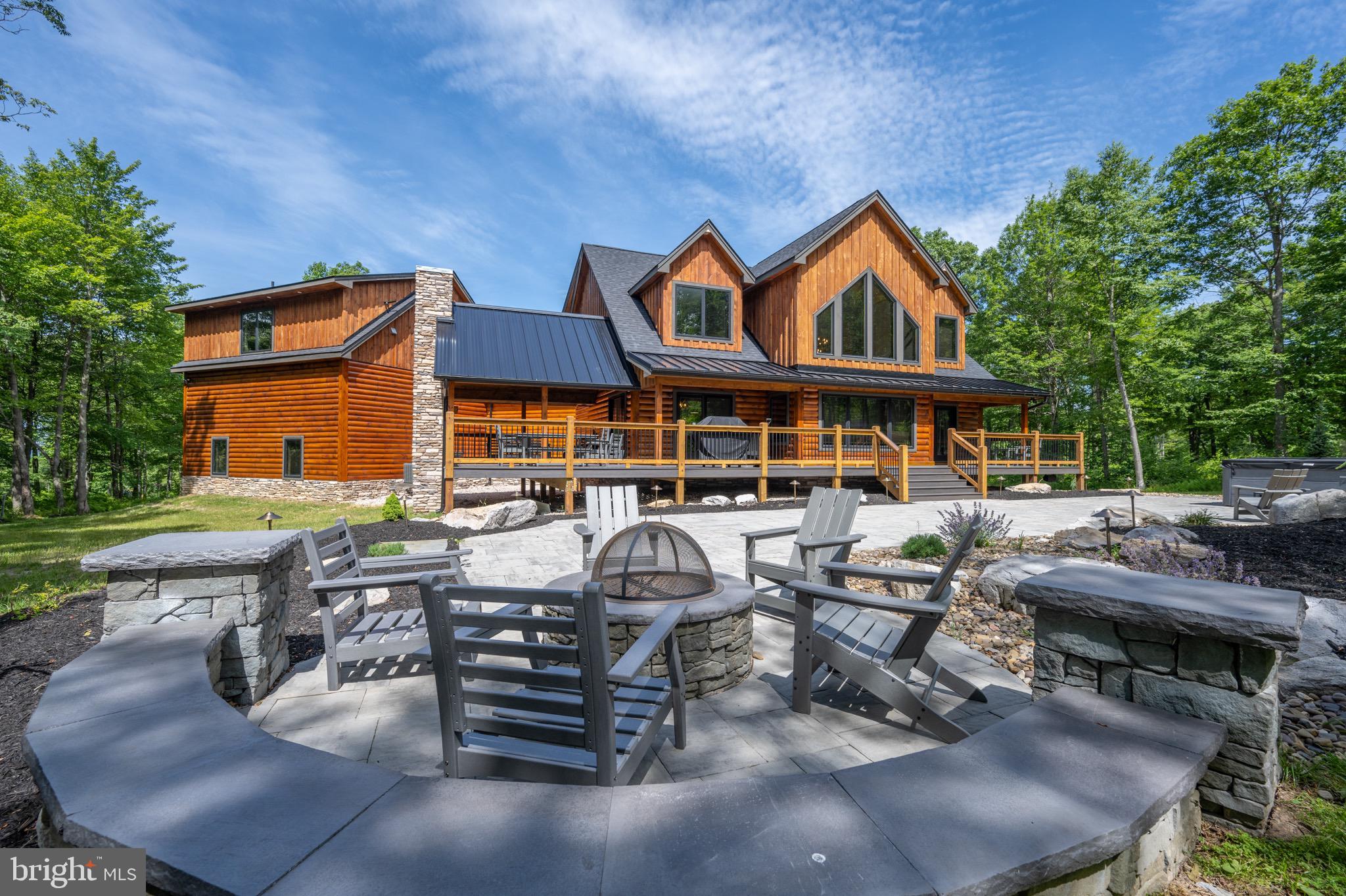Luxury Log Home at Deep Creek Lake – With almost 7,000 sq ft of living space, this 6bed 6.5Bath log home was recently finished in 2023 and features oversized Mountaineer Logs, outdoor gas fireplace with covered seating, Standing Seam metal roof accents, Electric Car Charger, and a 120” Laser 4K Theater System! Main level primary suite, that walks out to the back deck. Open concept  with vaulted ceilings enveloping the two story stacked stone fireplace. Perfect blend of rustic lodge and modern contemporary throughout. Elegant fully tiled primary bathrooms with standing tubs. Stylish Chef’s kitchen with high-performance appliances, quartz countertops, island bar, and hidden pantry. Second living space on the lower level equipped with a full wet bar, gas fireplace and shuffleboard table. Massive Laundry/Mudroom. Oversized heated garage. Sprawling blue stone paved patio with premium Hot Tub Spa and built in outdoor fire pit. No expense was spared on the finishes, furnishings, and gingerbread final touches. Home is being sold "turn-key", fully furnished. Minutes from local establishments, marinas, state parks and Wisp Resort – This modern incarnation of a Deep Creek Classic provides easy access to everything you love about Garrett County, with all the comfort, style and amenities of Home… Call today for your private showing!