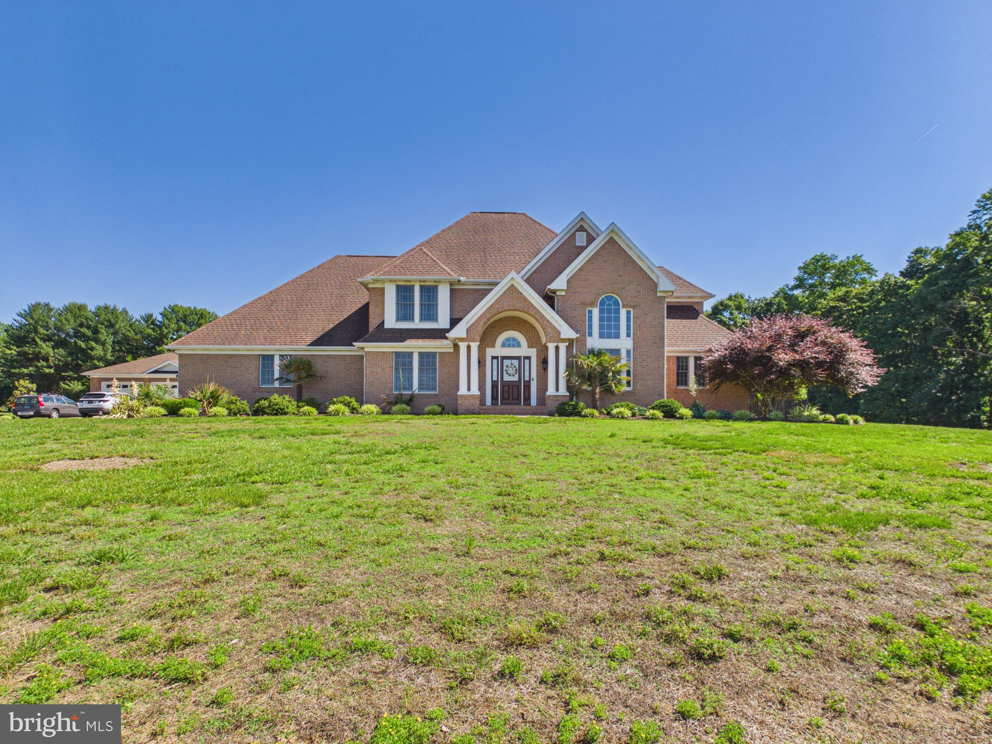 Welcome to your private, sun-drenched countryside sanctuary! Tucked peacefully back down a sweeping paved drive on a breathtaking 9.64-acre lot with NO HOA, this magnificent 2-story Colonial warmly greets you with a dramatic, double-height grand foyer and curved staircase. Radiant natural light pours through an abundance of oversized windows, beautifully illuminating the entire main level. To your left, find a spectacular double-height formal great room that flows seamlessly into an open-concept, double-height family room featuring a cozy fireplace and direct access to your rear patio. The heart of the home is the expansive gourmet kitchen, complete with a center island and ample storage. Perfect for long-term comfort or multi-generational living, the entry level boasts a spacious primary bedroom suite with a private ensuite bath and a large walk-in closet. Step outside into a backyard resort paradise featuring a sparkling in-ground pool, concrete patio, and a fully equipped luxury pool house. Storage is unmatched with a full-footprint walk-out basement in the main house PLUS a rare, dedicated extra storage basement in the pool house. For car enthusiasts or hobbyists, enjoy a spacious attached 3-car garage PLUS a separate, massive detached 3-car garage/workshop! Minutes to the Mispillion Riverwalk, Abbott's Mill Nature Center, Route 1 & 13, and Delaware beaches. Your dream estate awaits!