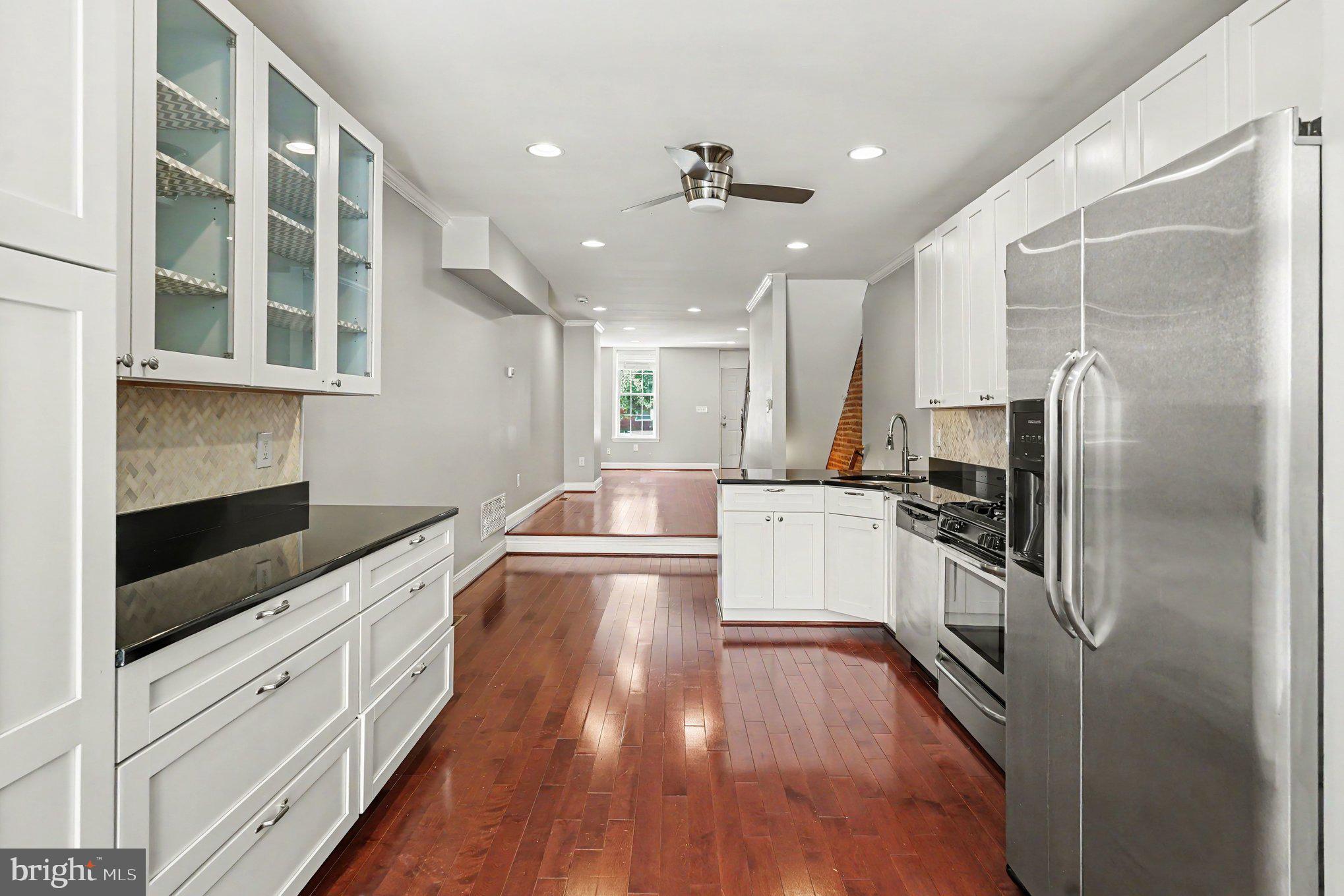 Welcome to 120 E Randall Street, a move-in ready Federal-style rowhome in Baltimore's historic Riverside neighborhood. This charming brick-front home offers approximately 1,500 square feet of living space with 2 bedrooms, 2.5 baths, and a thoughtful blend of historic character and modern updates.
The main level features rich hardwood floors, exposed brick walls, abundant natural light, and an open-concept layout ideal for everyday living and entertaining. The updated kitchen is equipped with white cabinetry, stainless steel appliances, granite countertops, and a stylish tile backsplash.  A convenient half bath and rear porch complete the main level. Upstairs, you'll find two spacious bedrooms, including a primary suite with a private en suite bath. A skylight fills the upper level with natural light while exposed brick accents add warmth and character throughout. The partially finished basement provides flexible space for a home office, gym, recreation room, or additional storage. Ideally located near Riverside Park, local dining, shopping, and all that South Baltimore has to offer, this updated rowhome delivers the perfect combination of charm, comfort, and convenience.