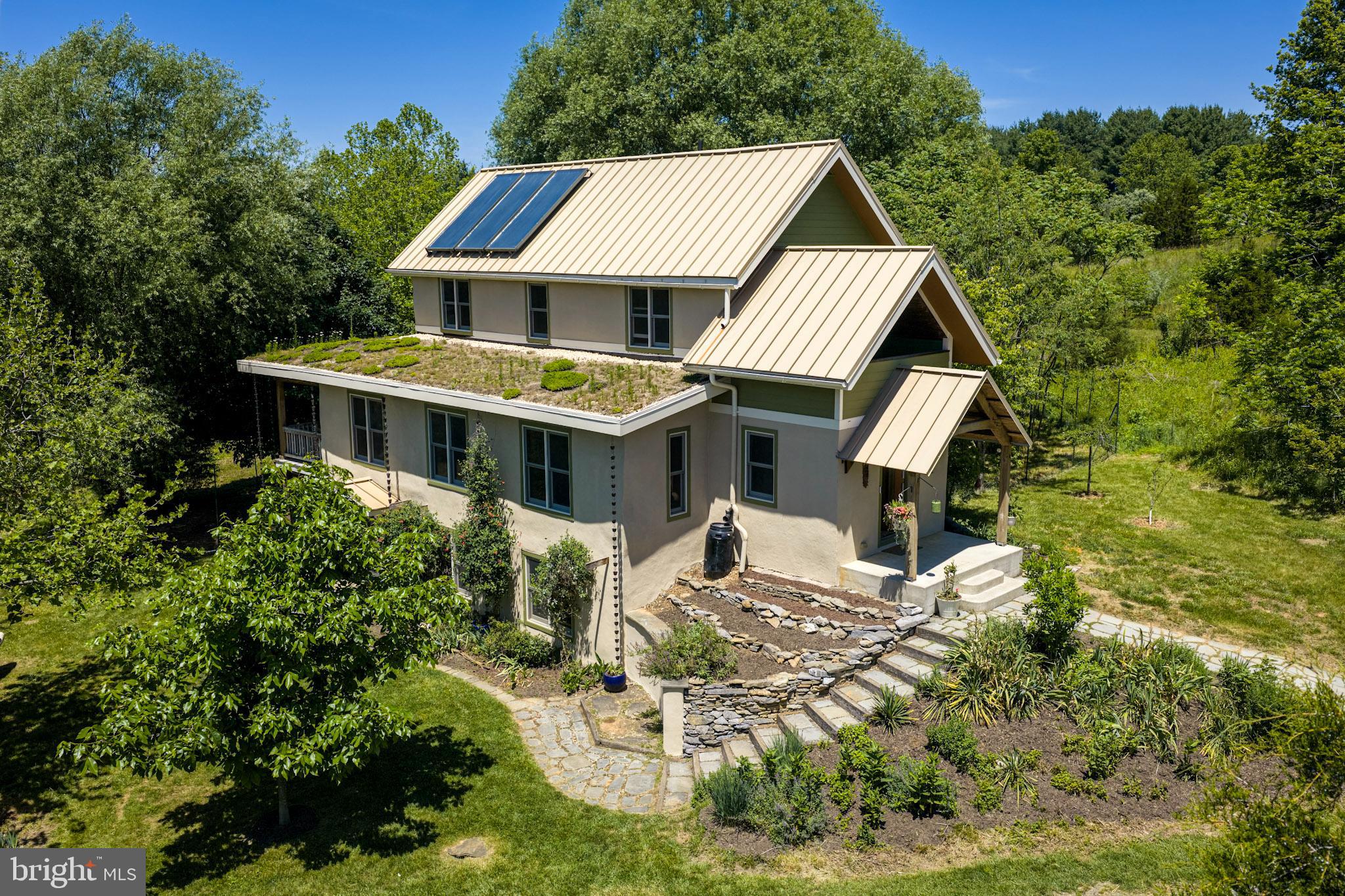 Enjoy smart and eco-friendly living in this custom country cottage situated on a private .42-acre lot PLUS an additional .33-acre lot (41069 Hickory Shade Ln. with well and septic) in the uniquely beautiful community of Eco Village.  The construction consists of stucco exterior, wood beams, concrete and hardwood floors with radiant zoned heating, iron terminator water system, natural composting system, reclaimed solid wood doors, a “green” roof, and PaperStone countertops.  Enjoy gardening, having chickens, beautiful vistas, and the peace and quiet that only a property like this can provide.  Eco Village is truly one of a kind with 90 acres of organically managed land including 50 acres in conservation with walking trails.  The community offers separate trash and recycling disposal areas as well as electric car charging stations.  The community association maintains private roads and amenities. Conveniently located just 5 miles from the MARC train station in Pt. of Rocks for an easy commute to Washington DC and just a short drive to Historic Towns of Waterford, Lucketts, and Lovettsville, this home is perfectly situated.

Featuring 3 bedrooms and 2 full bathrooms (including a main level bedroom), this custom cottage awaits! The stucco exterior has been freshly painted.   Crest up the stone walkway to the covered portico and enter the foyer space with concrete floors, unique branch coat-stand, and plentiful closet space.  Step into the marvelous main level with the efficient kitchen complete with paper-stone counter, LVP flooring, plentiful cabinetry, mini split system, and exposed beams.
Concrete floors with SoyCrete stain carry throughout the open living area featuring separate dining and family room space with another mini-split system.  The covered back deck sits off the family room and provides an ideal space to relax and unwind or dine alfresco. The main level bedroom offers hardwood floors, exposed beams, ceiling fan, and walk-in closet.  The full bathroom provided new LVP floors, stand-alone shower, and exposed beans.  The laundry closet completes the main level.

Hardwood stairs lead to the lovely upper level.  The 2nd bedroom offers hardwood floors, exposed beams, and ceiling fan.  The 2nd full bathroom offers a tub/shower combo with custom tile surround along with new LVP floors.  The 3rd bedroom offers hardwood floors, ceiling fan, and an east facing sleeping porch with gorgeous mountain views (could be enclosed if desired for more living space!). The upper level is heated and cooled by a ducted system in the attic.

Hardwood stairs lead to the walk-out lower level with concrete floors, mini-split system, large window seats, and under-stair storage.  French doors lead to stone patio. The spacious unfinished space for additional storage and/or workshop houses the mechanics of the home.

Other unique features of the home include a metal roof, solar panels to support the 115 gallon water heater and radiant flooring system,  a "living roof" (often referred to as a green roof) which serves a natural biophilic extension of the home providing aesthetic value while offering environmental benefits (better storm water management, thermal insulation, and keeps the home warmer in the winter and cooler in the summer) and straw bale insulation paired with stucco which is a highly sustainable -carbon neutral construction method that deliver excellent thermal performance.

The common lands in Eco Village provide a Wildlife Sanctuary certified through the Audubon at Home Program of the Audubon Society of Northern Virginia as well as serve as a Monarch Waystation that is certified by Monarch Watch.  

Enjoy outdoor activities like hiking, biking, and kayaking on the Potomac River.  With wineries, breweries, distilleries, farm to table restaurants, quaint shops, and plentiful things to do in the area, this isn’t simply a house, this is a lifestyle that preserves nature and all its beauty.  There truly is no place like home.