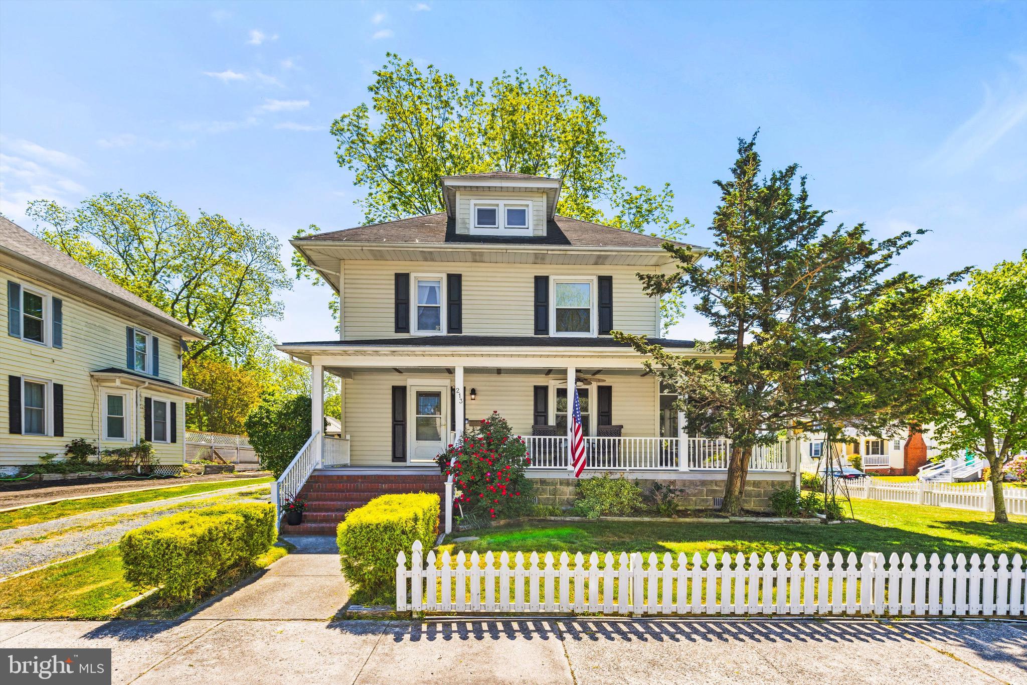 On a quiet back street corner, this charming Craftsman Four Square home welcomes you with timeless appeal. A white picket fence frames the yard, accented by boxwood hedges and mature shade trees—an ideal setting for play, pets, gatherings, or simply enjoying a peaceful afternoon. The wrap-around porch invites you to slow down, whether you’re sipping morning coffee, sharing dinner in the evening breeze, or greeting neighbors as the sun sets.
Step inside to a gracious formal entryway, where beautiful hardwood floors immediately draw you in and continue throughout the home. A classic newel post and railing lead upstairs, while the main level opens into a spacious, light-filled living room with oversized windows offering lovely views. The open flow continues into the formal dining room, where a corner gas fireplace and abundant natural light create the perfect backdrop for meaningful meals and conversation.
A breakfast bar connects the dining space to the large country kitchen, creating a warm and inviting hub where everyone naturally gathers—just as the aroma of home cooking fills the air.
Upstairs, three bright and airy bedrooms provide peaceful retreats. Sunlight filters through long, flowing curtains, creating a soft, relaxing atmosphere—perfect for quiet afternoons or restful evenings. A well-appointed full bath and ample storage add everyday convenience, while a single-car garage offers additional space.
Located in the heart of Pocomoke City, this home offers the charm of a close-knit community with easy access to some of the region’s most loved coastal destinations. Local dining, shopping, and year-round events are just minutes away.
This isn’t just a house—it’s the lifestyle you’ve been waiting for.