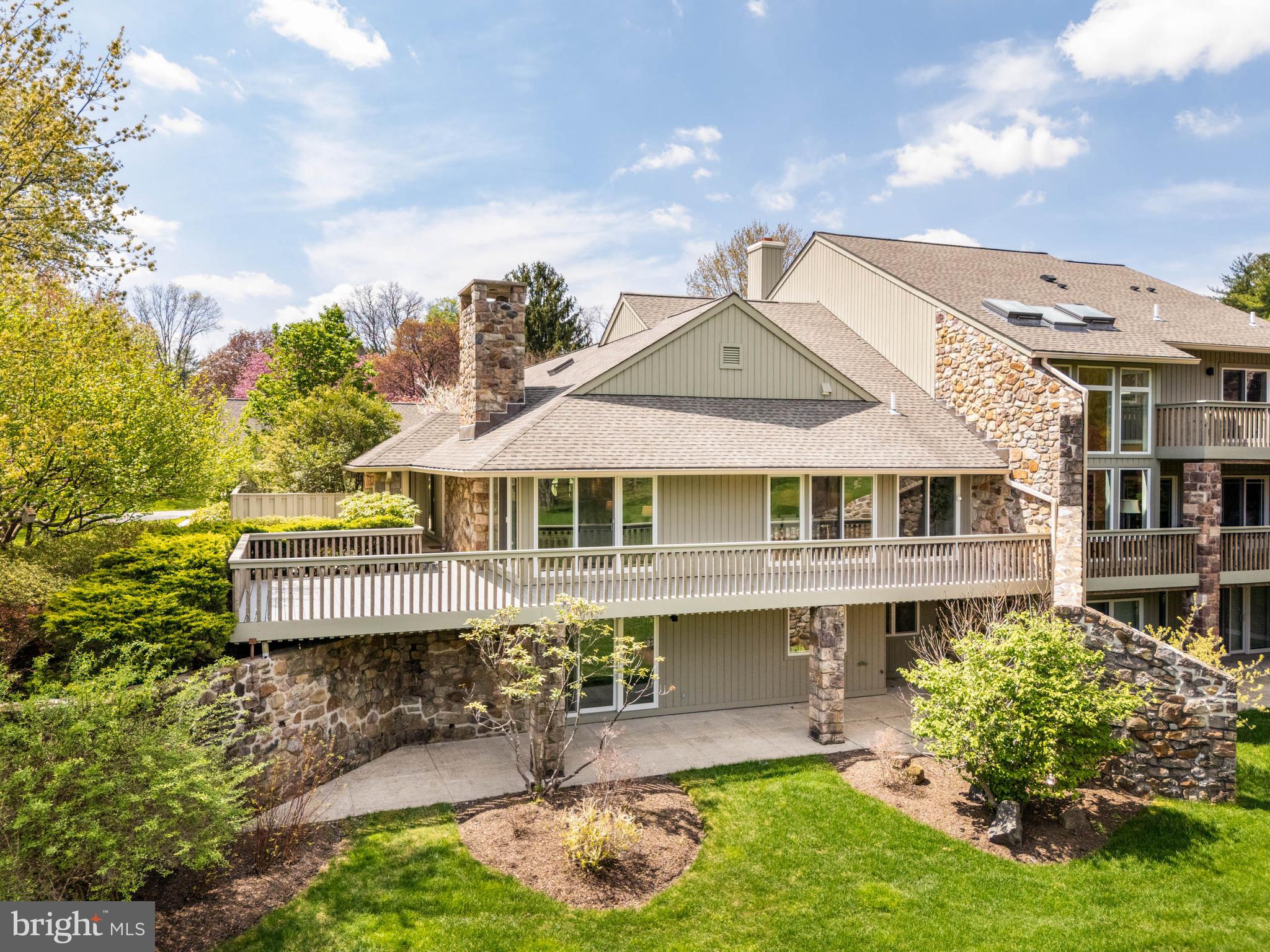 A rare opportunity to own the most desirable home in The Hermitage, a sought-after enclave in Bryn Mawr. Ideally positioned at the center of the neighborhood, this premier end-unit offers exceptional privacy and the community’s most coveted, uninterrupted panorama of nature—lush landscaping, mature trees, and a serene pond just beyond the flat, open backyard. Shielded by natural buffers, the home enjoys a sense of quiet seclusion, free from the disruption of passing traffic or neighborhood activity.

Fully renovated in 2019 by Spire Builders and designed by R.A. Hoffman Architects, the residence offers over 4,000 square feet of pristine, turnkey living. Every detail was curated for modern living, from the updated Trex deck and contemporary interiors to the versatile open backyard—perfect for a future pool, garden, or enclosed space for pets.

The main level presents a beautifully balanced layout, blending refined gathering spaces with private bedroom retreats. The expansive primary suite features three walk-in closets, en-suite laundry, a spa-inspired bath, and direct access to a secluded patio. A generous guest bedroom with en-suite bath offers comfort and privacy for visitors. A handsome library or office with custom built-in cabinetry and a wood-burning fireplace adds depth and warmth, while the spacious living room showcases a natural stone fireplace and sweeping views to the horizon. The large dining room flows seamlessly into a sleek, modern kitchen with walk-in pantry – perfect for entertaining or everyday living. A stylish and conveniently placed powder room completes the main floor.

The day-lit walkout garden level continues the home’s flexible living experience, offering another private guest bedroom with built-ins, a full bath, and a generous living or recreation space with custom built-ins and direct access to the rear grounds.

Four private parking spots include a two-car garage with an upper-level loft—ideal for a studio, gym, or creative workspace. Both the garage loft and walk-up attic offer potential for further customization and expansion, including the opportunity to create additional bedrooms with en-suite baths and natural light.

The Hermitage is more than just a place to live—it's a community designed and built around connection and enjoyment. Residents enjoy peaceful walking loops that wind through beautifully landscaped grounds, secluded tennis courts tucked among the trees, and charming outdoor features like gazebos, a scenic bridge, and a bench overlooking the picturesque pond—perfect for morning coffee or quiet reflection. It’s an active, friendly neighborhood that feels like a private retreat.
Set in a tranquil, park-like setting just minutes from downtown Bryn Mawr, this home blends timeless design, modern ease, and the rare combination of beauty, privacy, and possibility.