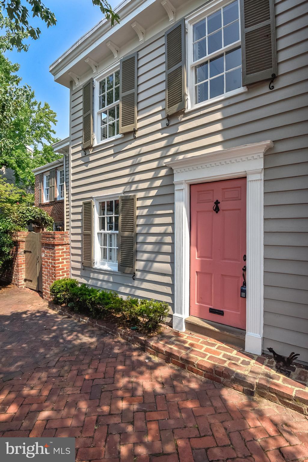 Built in 1820 and located on the most coveted block of Old Town, this historic gem is on the market for the only time in 65 years! With marvelous sunlight streaming throughout, this end townhome enjoys an unobstructed birds’ eye view of Windmill Park + the Potomac River to the east while the length of the south-facing home provides sunlight to each room in the home. Charm and elegance resonate throughout with many original elements of a bygone era. Upgrades + extra features added by the owners compliment the home’s preserved historic character. The entrance to the wood clapboard home features a brick threshold + a row of boxwoods. Wood cornices accent the roof line + shutters with distinctive iron scroll shutter guards accentuate the east and south-facing windows. Enter the wide foyer featuring paneling on the walls + a bead board ceiling. The south + each-facing living room is filled with light throughout the day + offers a broad view of the park and River. It features walls of built-in cabinetry and bookcases + a handsome fireplace accented by a wood mantle, Roman ionic column paneling + thick dental moulding. The antique heart pine flooring carries into the family room with fireplace + bookcases. A second doorway leads to the dining room, large by Old Town standards, which can easily provide seating for a table of ten.  This room is sure to delight with wood paneling, bookcases, a bar with storage drawers and shelving and walls of built-ins with, as throughout the home, old drop bar latches, strap hinges + handles. Brick flooring + a fireplace complete this special room. The rear of the home features a half bath and a spacious kitchen with ample cabinet space and windows overlooking the private patio. A Dutch door leads to the side and rear gardens. With original newel post and railing, wainscot wall paneling carries to the upper level with heart pine floors throughout + a hallway with a wall of closets. To the left of the stairway is a large bright bedroom with a hall to the full bath featuring ample closets and a charming dressing table. The laundry with great workspace is located off this room. Following the hall closets to the front of the home is a bedroom with a wall of bookcases and closet – perfect for a crib, office or exercise room. The large owners’ suite, with plenty of space for a king size bed + sitting area, faces the Potomac + Windmill Park allowing for glorious morning light + soft golden light at the end of the day. The owners' bath with large linen closet and tiled shower with seamless glass door was remodeled by Harry Braswell, Inc.  Follow the stairs to the top floor featuring a small area with wood paneling + a window – a perfect spot for a desk or extra dresser. A comfortable sized bedroom with hardwood floors + windows on three sides plus a tiled full bath complete this private space. Reached by a hatch in the front hall, there is a cellar under the living room for all storage needs! Offering a quiet oasis from the busy world, the spacious brick patio + side yard are enclosed by a high brick wall. Adorned with mature landscaping, the rear yard is separated from the side yard by a brick archway with cascading ivy.  The beauty of yesteryear is especially prevalent in the southeast quadrant, home to some of Old Town’s oldest + most significant historic dwellings. Whether adult or child, there is also fun + relaxation for all right across Lee Street with a hill which rolls down to the Potomac for sledding, play + picnic spots as well as volleyball + basketball courts. The bike path is one block away + the beautiful waterfront, restaurants + shops of King + Washington Streets, grocery stores, dry cleaners, schools and churches are within blocks. The fireplaces + a/c units convey "as is".