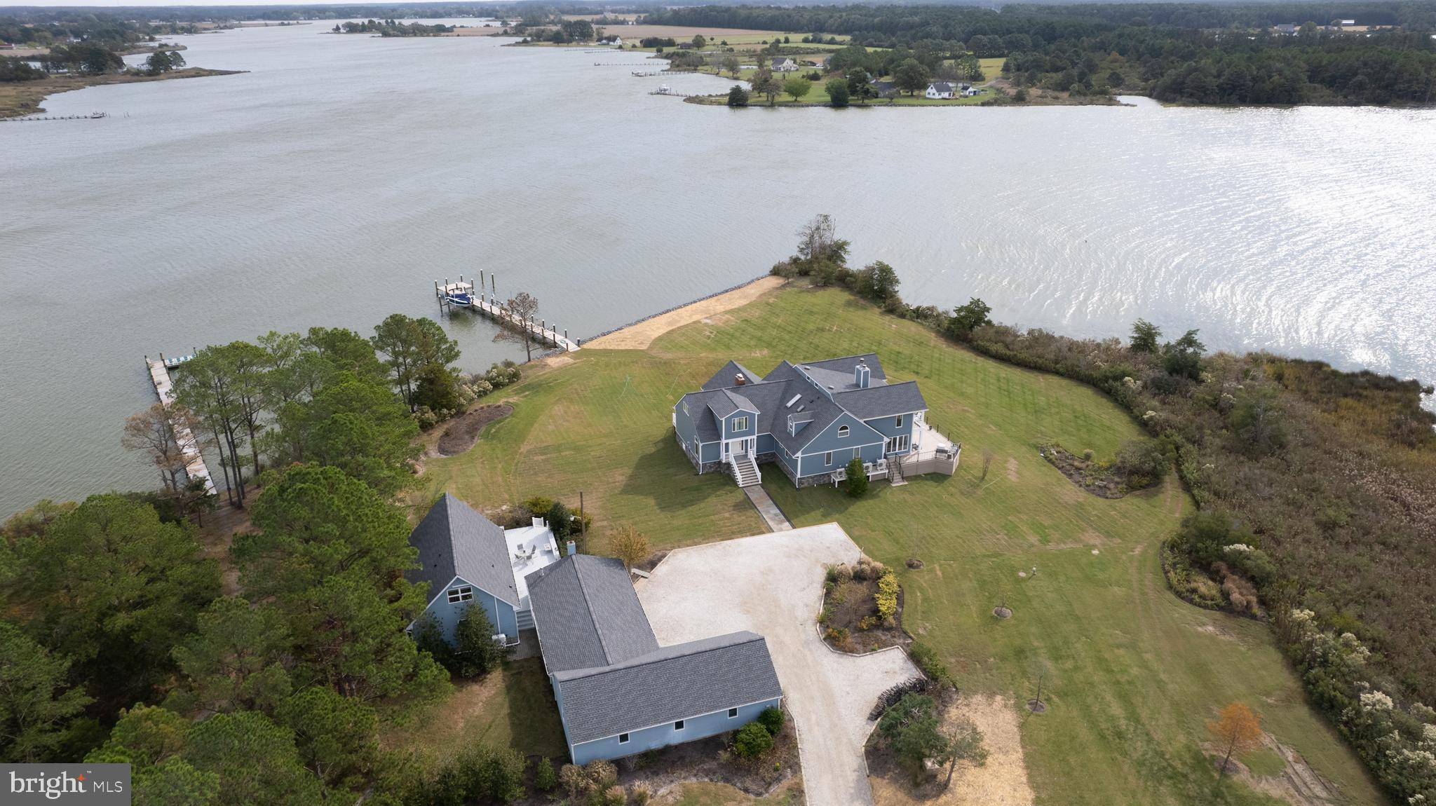 Nestled on the private four-acre waterfront enclave of Three Creeks Point, this extraordinary estate offers breathtaking sunrises and sunsets over Fishing Creek with sweeping southerly views of Church Creek spanning more than 180 degrees. The primary residence features 5 bedrooms, 4.5 baths, and over 5,400 square feet of thoughtfully designed living space, complemented by an expansive maintenance-free wraparound deck providing panoramic water views from nearly every angle.
Enhancing the main residence is a separate 2-bedroom, 1.5-bath guest home featuring a Primary Bedroom on the 1st floor with full bath and additional bedroom in the loft with adjoining half bath. The guest home is complete with a full kitchen, laundry, private deck, and tranquil water vistas — ideal for hosting guests or multi-generational living. Just minutes from the open Chesapeake Bay, this property boasts approximately 6 feet mean low water (MLW) along the protected waters of Fishing Creek, creating exceptional opportunities for boating, fishing, crabbing, paddleboarding, and kayaking along the quiet creeks of the Little Choptank River.
The L-shaped pier is fully equipped with an electric boat lift, jet ski lift, and multiple slips, offering ease of waterfront access. Recent extensive exterior improvements and renovations have enhanced both the low-maintenance appeal of the property and maximized the stunning waterfront views.
Inside, the home showcases a spacious open layout perfect for everyday living and entertaining. The Great Room is filled with natural light and opens seamlessly to the wraparound deck, creating a remarkable indoor-outdoor flow. The Brand-New 2025 Kitchen is the heart of the home, completely remodeled with high-end finishes and designed to serve both the casual homeowner and the enthusiastic entertainer alike. New hardwood flooring throughout the first floor elevates the living spaces while maintaining warmth and coastal elegance.
Formal living and dining areas provide refined entertaining space anchored by a stunning stone fireplace, while the sunroom, spanning the width of the home, delivers captivating eastern, western, and southern water views that shift beautifully throughout the day.
The main level includes two bedrooms and a full bath tucked into a private alcove, offering comfortable guest accommodations or flexible living options. The upper level hosts the impressive primary suite, complete with vaulted ceiling, fireplace, private waterside balcony, spa-inspired ceramic tile bath with walk-in shower, and spacious walk-in closet. Two additional bedrooms and a full bath are also located on the second floor. An oversized office with vaulted ceiling and its own balcony provides an inspiring remote workspace overlooking the water.
The guest house is equally inviting, featuring a first-floor bedroom and bath, full kitchen, stacked washer and dryer, and a second-floor bedroom with loft area — perfect for extended stays.
A detached four-car garage offers ample storage for vehicles, water toys, and workshop needs.
With its unrivaled waterfront views, deep water access, private setting, generous living spaces, updated interior features, guest accommodations, and extensive dock amenities, this exceptional property represents the pinnacle of luxury Eastern Shore living.