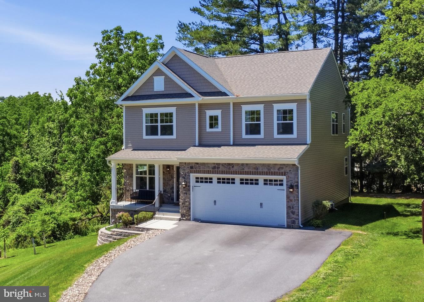 Welcome to this meticulously crafted, nearly-new luxury residence located in the highly sought-after Ellicott City neighborhood of Montgomery Knolls. Just two years young, this stunning home offers over 3,500 square feet of pristine living space, featuring six bedrooms and three-and-a-half bathrooms. Situated on a lush 0.45-acre lot, the property immediately captivates with a welcoming, fully covered front porch adorned with beautiful stone veneer. Inside, extensive custom trim work including elegant wainscoting, deep tray ceilings, and bespoke accent walls, seamlessly blends modern sophistication with timeless architectural details. As you step through the front door, premium luxury vinyl plank flooring guides you through the open-concept main level and up the main staircase. An elegant flex space greets you off the foyer, boasting exquisite trim work that makes it the perfect formal living room, sitting room, or executive home office. Entertaining is effortless in the spectacular chef's kitchen, a culinary masterpiece featuring full-overlay, white shaker-style cabinetry with soft-close hardware, high-end quartz countertops, and a striking full-height quartz backsplash. Premium stainless steel appliances, including a professional-grade 36-inch gas cooktop with an exterior-vented designer range hood, elevate the cooking experience. The expansive center island comfortably seats four, seamlessly overlooking a sprawling, light-filled family room anchored by a magnificent, coffered ceiling. A custom wet bar with floating shelves and a beverage fridge, alongside a glass-door walk-in pantry with custom shelving, completes this entertainer’s dream. Practical luxury is also evident on this level, from the stunning designer powder room featuring a stone accent wall, to the massive walk-in coat closet conveniently located just off the garage. Ascending to the upper level reveals a private sanctuary designed for ultimate comfort. The expansive primary suite is a true retreat, crowned with a sophisticated tray ceiling and offering dual custom closets. Its lavish en-suite spa bathroom features upgraded tile, the same exquisite quartz surfaces found in the kitchen, a dedicated soaking tub, a separate glass-enclosed shower, and a private water closet. Three exceptionally large secondary bedrooms provide abundant personal space, with each boasting its own dedicated walk-in closet. These rooms share a beautifully appointed hall bathroom featuring a double vanity and upgraded tile. Adding to the convenience of the upper level is a dedicated laundry room, complete with a utility sink, washer, and dryer. The walk-out lower level serves as a highly versatile extension of the home’s living space, bathed in natural light and offering easy egress to the backyard. It hosts a generous recreation room perfect for a home theater or secondary lounge, along with two additional bedrooms equipped with ample closet space, ideal for welcoming guests, setting up a home gym, or crafting a secondary home office. A beautifully full bathroom with upgraded ceramic tile perfectly services this level. Beyond the attached two-car garage, an expansive driveway accommodates up to five vehicles, ensuring plenty of parking for entertaining. The property boasts a fantastic, private tree-lined backyard that provides a serene and picturesque backdrop for outdoor living. This spectacular residence transfers with a new construction warranty offered through QBW covering major structural elements including the foundation, floor joists, and bearing walls. Enjoy the incredible financial benefit and rarity of having NO Front Foot Fees and NO HOA Fees, making this immaculate Montgomery Knolls masterpiece the perfect place to call home.