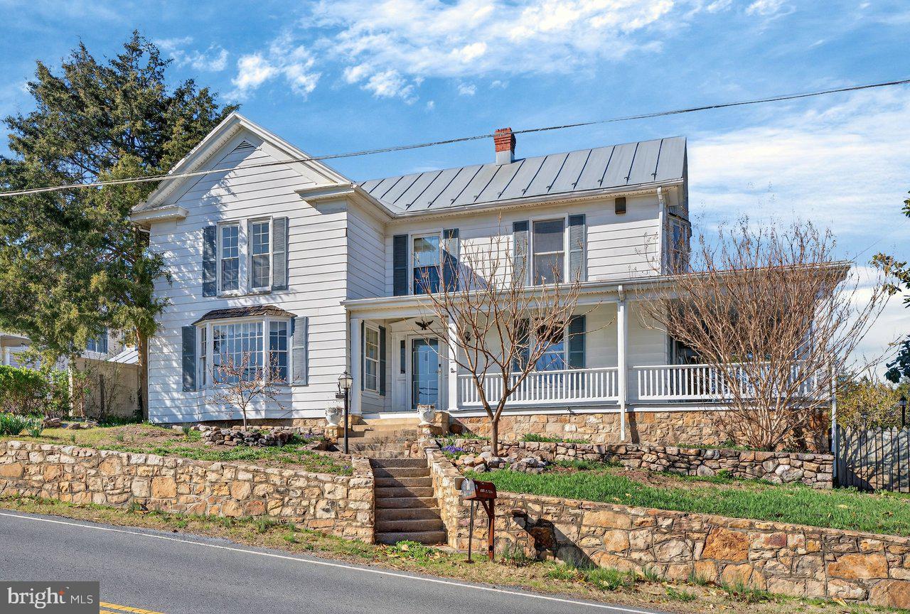 Step into a piece of Luray history, where timeless character meets everyday livability. This beautifully maintained 1890s Colonial offers nearly 3,000 square feet of charm, natural light, and flexible living space—just moments from historic downtown Luray, near Skyline Drive, and the entrance to Shenandoah National Park. Inside, original hardwood floors, custom built-ins, and sun-filled rooms create a warm, inviting feel throughout. The kitchen brings a unique vintage flair with custom yellow cabinetry, a 1950s diner-inspired aesthetic, and a functional butler’s pantry that flows seamlessly into the formal dining and living areas—ideal for entertaining. The main level also features a renovated full bath, a spacious family room with a functional wood-burning fireplace, and a flexible den, office, or potential fifth bedroom. Upstairs, you’ll find generously sized bedrooms, including a Jack-and-Jill layout, along with a renovated bathroom featuring a clawfoot tub and double vanity, plus a convenient laundry area. Storage is abundant throughout, with attic access, eave storage, and built-ins. Outside is where this property truly stands out. Set on a rare half-acre double lot, the wraparound porch captures sweeping mountain views, while the backyard is designed for gathering—complete with an in-ground pool, pool house, pond, fire pit, and garden space. The heated and cooled sun-garage with mini-split offers the perfect setup for a game room, studio, or year-round flex space. Properties like this rarely come available in-town—offering a unique combination of historic character, usable space, and walkability to shops, restaurants, and local favorites. Whether you're looking for a full-time residence or a weekend retreat just a couple hours from DC, this is Luray living at its best.