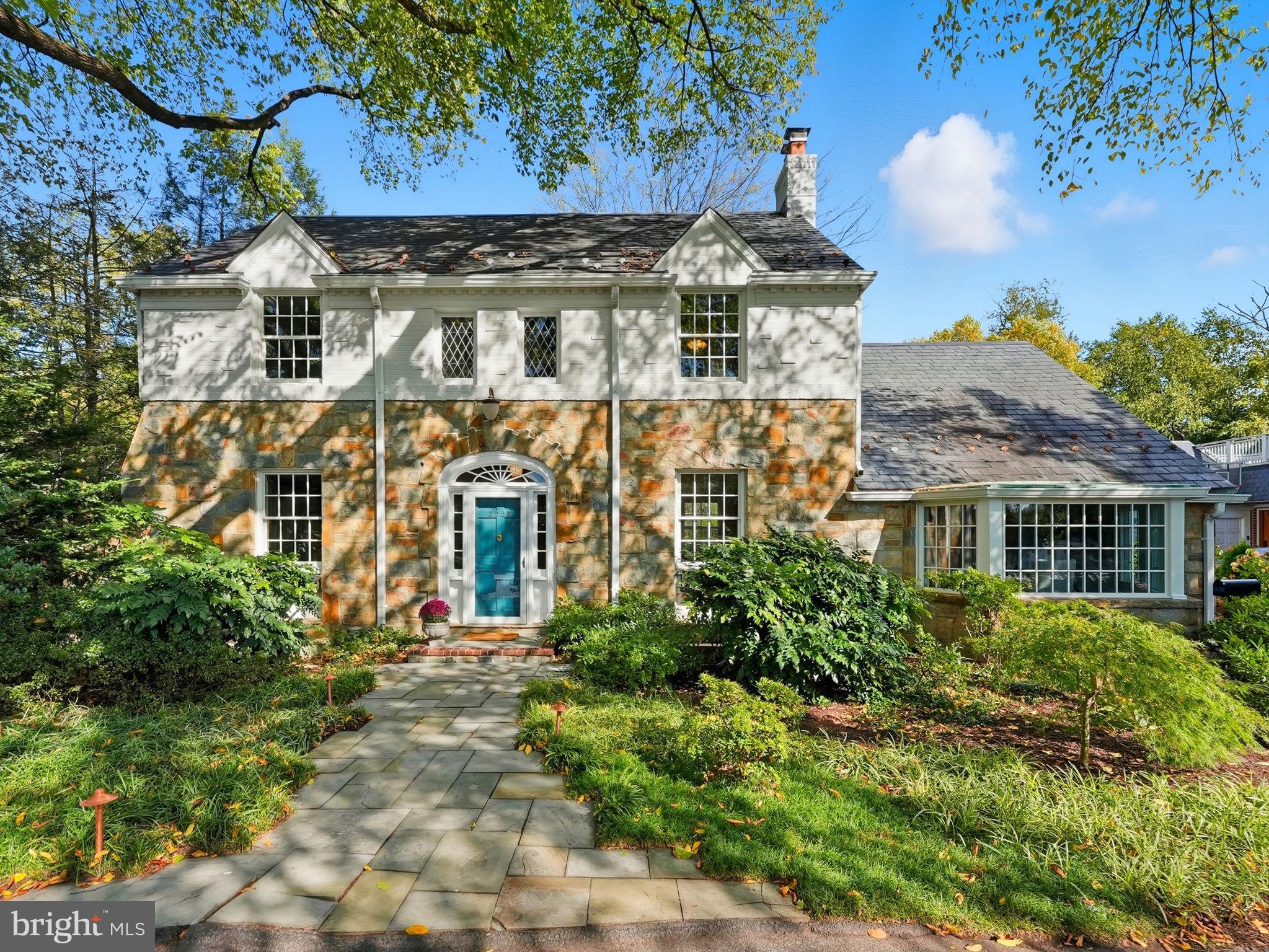 This stately Country Club Hills home sits on a 0.4-acre lot surrounded by mature trees and tranquil private spaces. It is steeped in history but lovingly maintained and improved over the years to allow for gracious living.  >>> Originally built in 1937, the exquisite stone and whitewashed brick colonial was awarded a Silver Star for Design and offers over 4,000 square feet of living space, blending gracious entertaining areas with warm, comfortable living.  Just a half block from the Washington Golf and Country Club, the property boasts a historic American Elm with an  expansive canopy (winner of the 2010 Arlington Notable Tree Award) in the front and extensive rear grounds ideal for afternoons of barbecues and sports (soccer, badminton, volleyball and croquet) or just plain relaxing or gardening in absolute privacy.  It even served at one time as the Country Club Hills preschool. >>> Inside, a beautiful formal dining room with intricate wallpaper and handcrafted molding opens to a warm, eat-in kitchen with a Sub-Zero refrigerator and other high-end appliances, island, and access to a screened porch and stone patio—perfect for gatherings or quiet reflection. The main level features an expansive sunlit living room with original mantel and gas fireplace, a charming library/office with bay window and custom built-ins, and a large family room with access to the gardens. >>> Upstairs are four spacious bedrooms and three full baths, including a serene primary suite with built-ins, window seat overlooking the backyard, and ensuite bath. A finished third level is perfect for cozy sleepovers or as a playroom or "teen suite." >>> The lower level offers a large recreation room, bonus gym or office, laundry with cabinetry and sink, a half bath and walk-out access to the backyard and detached garage. Above the garage, a private suite with full bath serves perfectly as guest or au pair quarter or as a separate office for the WFH owner.  With a circular drive, ample parking, and proximity to Georgetown, downtown DC, Reagan Airport, and fine dining, this timeless residence offers the perfect blend of historic charm with modern comfort in one of Arlington’s most coveted neighborhoods.