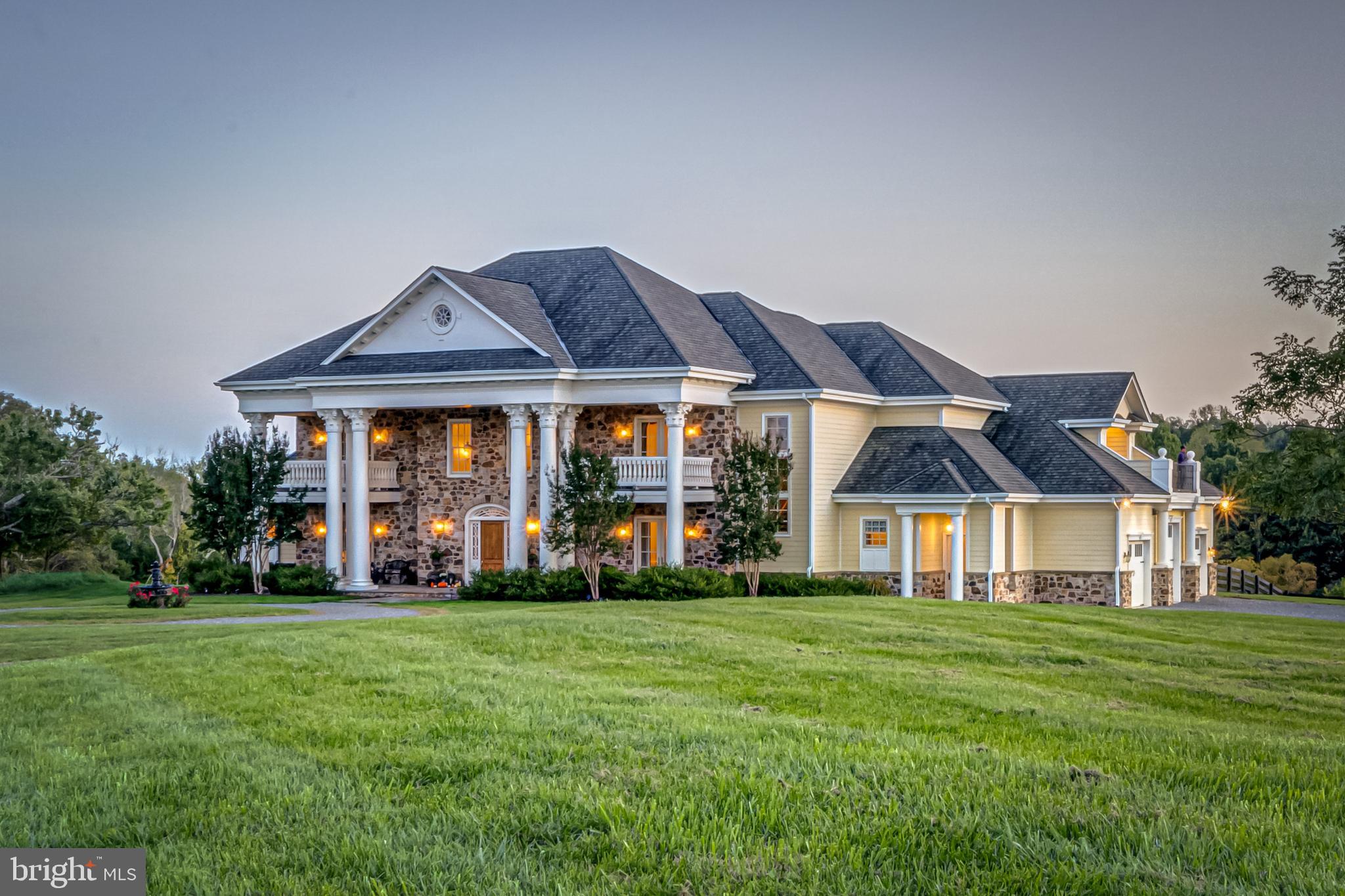 Significant price reduction, Fauquier County tax assessment is $2,244,100.  On the DC side of Warrenton, this impressive custom-built 7,700 square foot home is located on 8 private acres surrounded by scenic vistas.  The main level has a grand entry foyer, ground floor owner suite, and an attractive open kitchen with double ovens, 2 dishwashers, a large farmhouse sink, granite counters, and custom cabinetry.  The kitchen is open to the family room with a large Rumford fireplace and a light filled conservatory with a second Rumford fireplace and rough-in for a bar.  There are also formal living and dining rooms, a built-in office, and a mudroom on the main level as well as laundry on each floor.  The entry foyer has 24-foot ceilings, and the home has 14-foot ceilings on the main level with custom crown moldings generously sized throughout and a mix of Brazilian cherry hardwood floors, marble, and travertine tile in the conservatory.  The front door is a customized design imported from Argentina.  The primary suite is conveniently located on its own wing with a gas fireplace, elevated sleeping area, two closets, and a large bathroom with 2 sinks, separate water closet, expansive shower with 2 shower heads, and heated flooring.    There are 4 additional large bedrooms upstairs each with an en suite bathroom and private balcony for individual outdoor space.  The upstairs bedrooms are connected by 2 sitting areas, one of which is roughed in for a wet bar.  There is electrical work installed behind the house for a pool in an ideal location surrounded by patios, an outdoor fireplace, half bathroom, and outdoor shower.  The circular driveway entrance has established landscaping and water fountain with an oversized 3-car garage on the side.  There are two 1-acre fenced pastures with a run-in shed for animals of any breed or size.  The property is surrounded by land in a conservation easement with 4 estate lots.  The home is built of high-quality construction.  Ideal location 30 minutes to Dulles airport and 45 miles to Washington DC.  Property is surrounded by horse farms with an abundance of wildlife to enjoy.