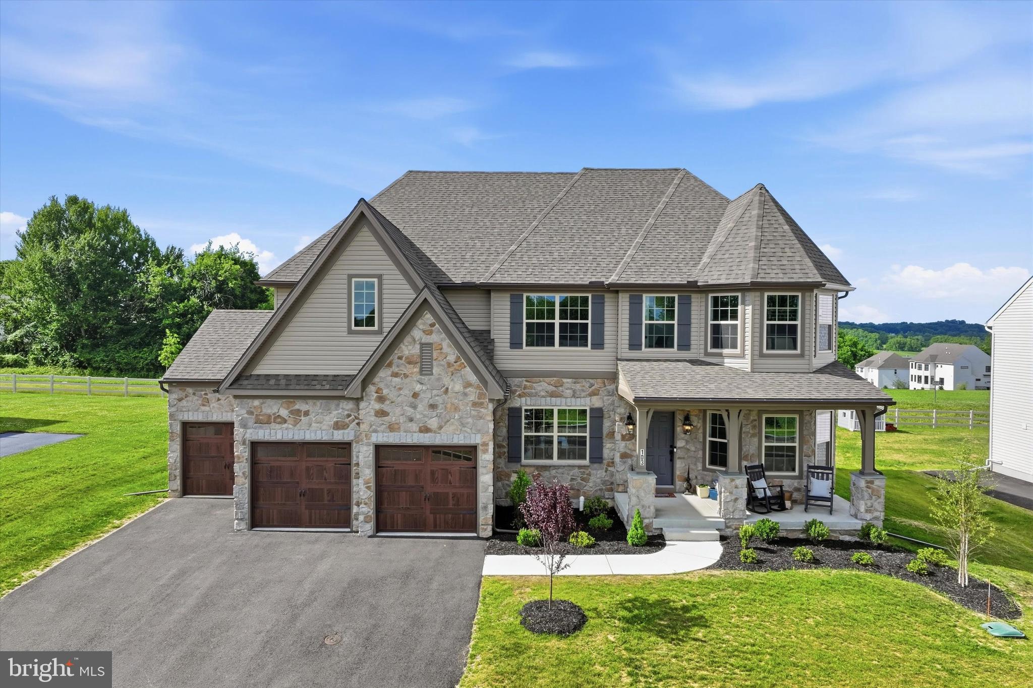 Welcome to 103 Janine Way, a stunning modern farmhouse located in the desirable Lexington Point community within the Avon Grove School District. Built by Keystone Custom Homes and completed in November 2025, this beautifully upgraded Hawthorne Manor model offers over-the-top craftsmanship, thoughtful design, and move-in-ready convenience on a beautiful homesite that backs to open space. The attractive stone and siding exterior, covered front porch, and three-car garage create exceptional curb appeal. Step inside the impressive two-story foyer featuring oak stair treads and elegant black metal balusters. The open floor plan is filled with natural light and showcases upgraded plank flooring throughout the main level. The first floor offers a spacious living room and formal dining room accented by a custom trim feature wall. At the heart of the home is the spectacular two-story family room featuring a floor-to-ceiling stone gas fireplace and an abundance of windows that flood the space with natural light. The chef's kitchen opens seamlessly to the family room and features an oversized center island, quartz countertops, stainless steel appliances, gas cooking, an upgraded stainless vent hood, and a spacious walk-in pantry. Additional first-floor highlights include a private office, convenient mudroom with garage access, powder room, and sliding glass doors leading to the 16' x 16' patio and backyard—perfect for outdoor entertaining. Upstairs, the luxurious primary suite offers a spacious bedroom and the upgraded Serenity Bath package complete with dual vanities, a large tiled shower, and a freestanding soaking tub. The expansive walk-in closet provides direct access to the laundry room, which can also be accessed from the hallway. Three additional generously sized bedrooms and a full hall bath complete the second level. The finished lower level adds incredible flexibility with a large recreation area, fifth bedroom, full bathroom with tub/shower combination, and a substantial unfinished storage area. With 5 bedrooms, 3.5 bathrooms, a finished basement, three-car garage, numerous builder upgrades, and nearly-new construction without the wait, this exceptional home offers the perfect blend of luxury, comfort, and functionality in one of Southern Chester County's most sought-after communities. Schedule your private tour today and experience everything this remarkable home has to offer.
