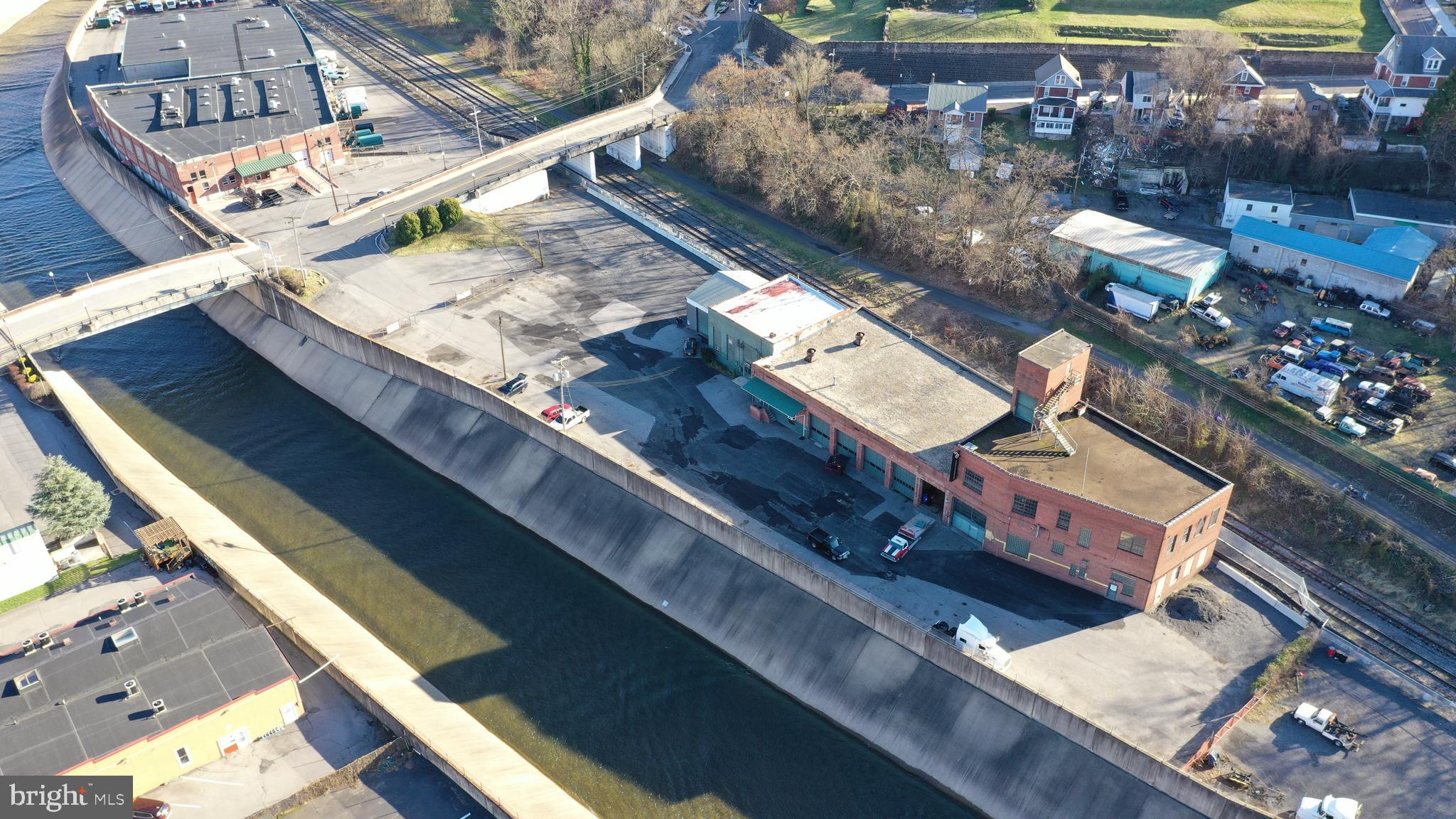 First time on market since 1980 Originally the Ice House for Queen City Brewery, converted to 6 bay truck repair facility in 1980 and successfully operated into 2024. 1.47 acres plus useful areas in public easements. Large brick - steel industrial building (1900) building with 7 large drive in doors, 12,952 measured main floor PLUS 3,386 Concrete roof decks with well maintained roofing. Built to handle massive floor loads. Just 1,500' from the center of town - big useful building with a very big parking lot. Property is adjacent to but outside of Historic District. Over 500' frontage on Wills Creek, WMSR Scenic RR, GAP Trail eastern terminus/ C&O canal Western Terminus  @ Canal Place is 1/4 mile walk away. Great opportunity to continue with truck repair/inspections/parts use or redevelop into Night Club Health Club Recreational Uses, Restaurant, Loft Apartments, Antiques, Art Gallery, Retail....