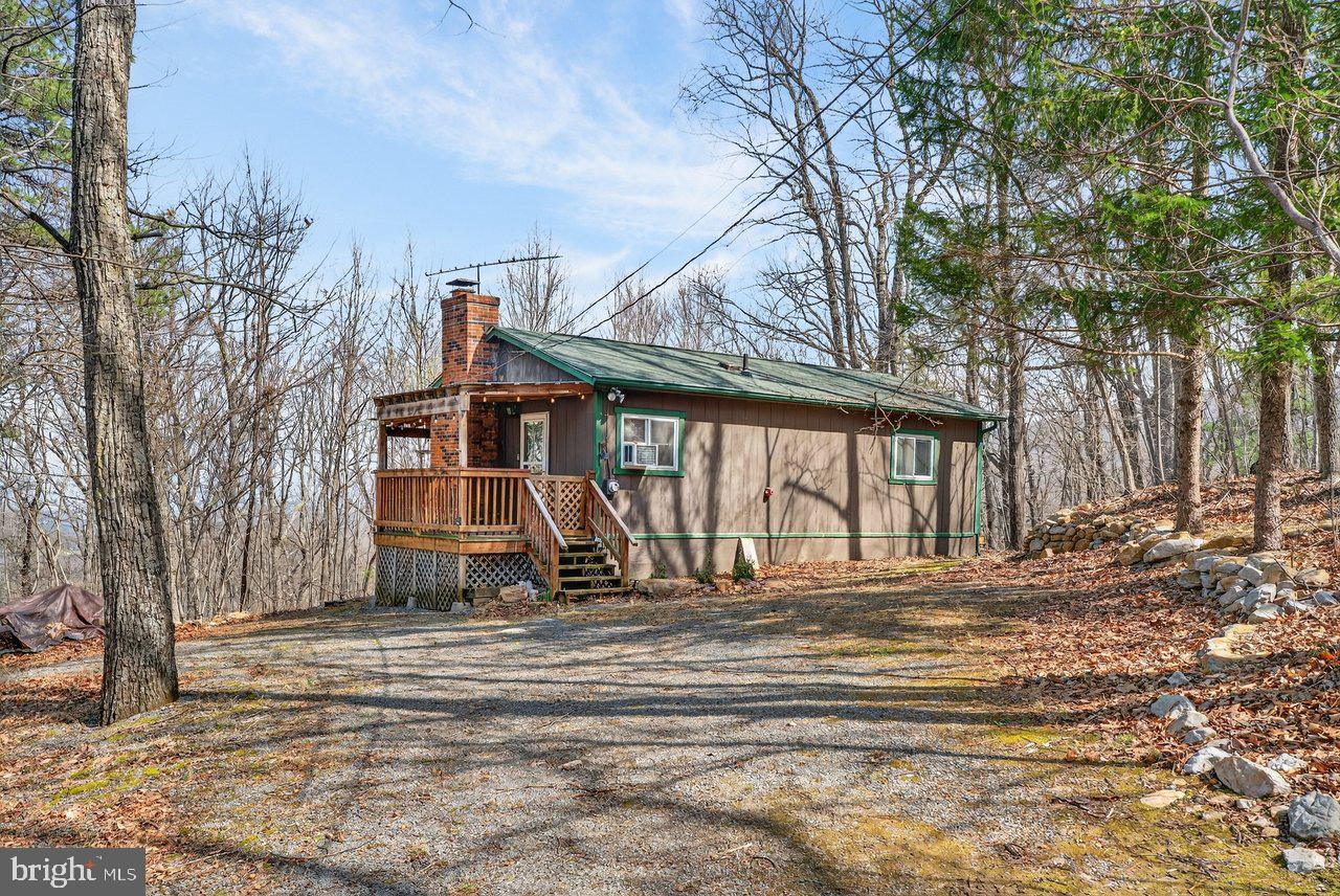 Tucked away on 3 wooded acres with seasonal views and National Forest land just across the street, 137 Sandstone Ln offers privacy and peaceful surroundings in a charming cabin setting! This 2-bedroom, 1-bath home is ideal as a full-time residence or weekend retreat, featuring a covered front porch that opens into an inviting living, dining, and kitchen area with a cozy fireplace accented by a rustic mantle installed in 2012. New kitchen appliances were installed in 2025, and the electric service upgraded too! The bathroom was updated in 2020, and additional improvements include: a new living room wall heater in 2021, a roof replaced in 2018, new windows and front door with storm door in 2010, and gutters installed in 2009. Outside, enjoy a spacious, partially covered deck with gorgeous mountain views AND a newly installed hot tub to take it all in! With thoughtful updates and a serene setting, this cabin is ready to welcome you home!