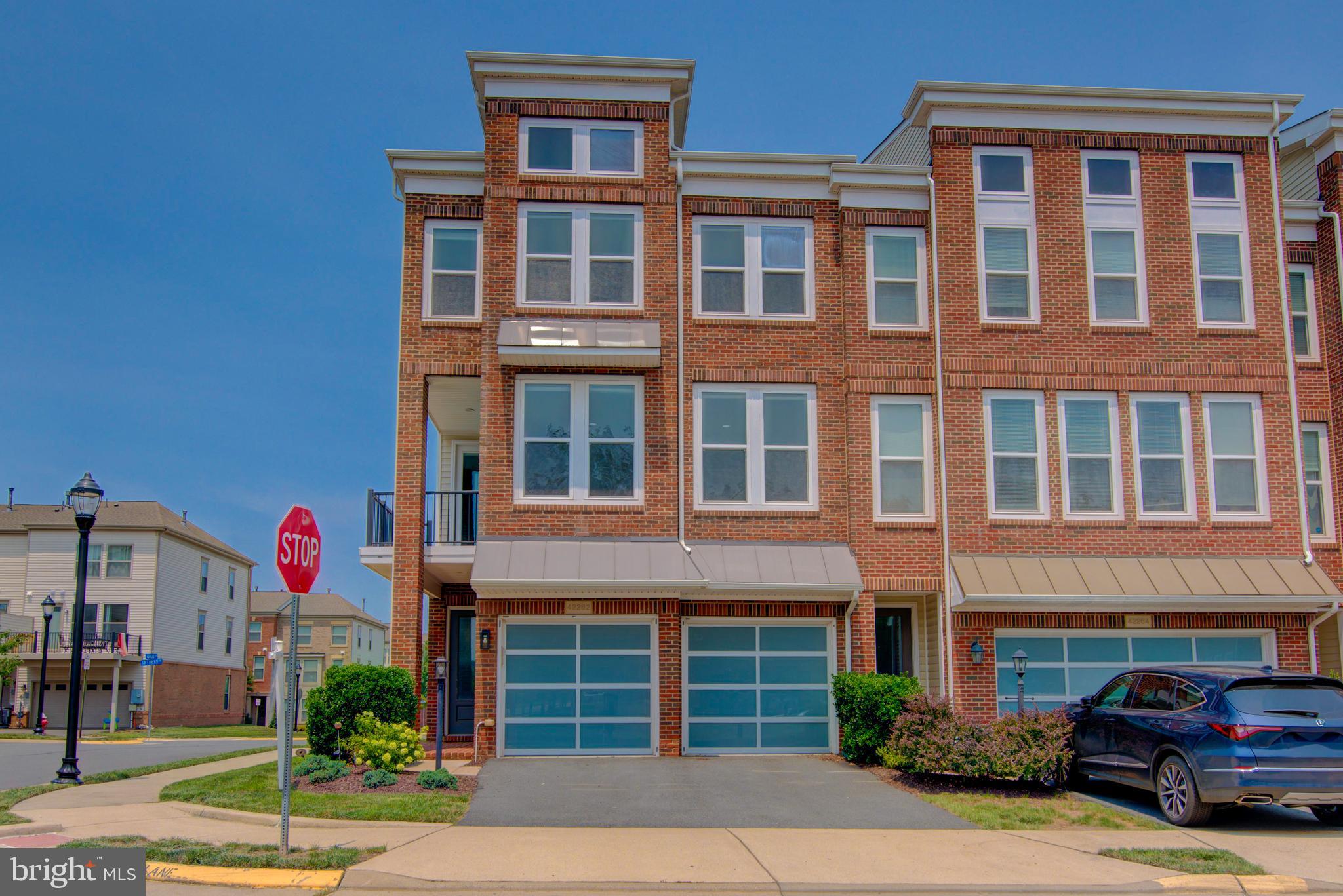 The very Best of Brambleton! Spacious (3263 sq ft!) end-unit garage townhome with a unique contemporary floorplan designed for modern lifestyles, including ENTRY LEVEL main living areas. The main level boasts 5" wide plank engineered wood floors and an open concept designed to enhance connections or make entertaining a breeze. Spacious family room adjacent dining area and the gorgeous gourmet kitchen - featuring oversized center island, Stainless steel farmhouse sink, wine fridge, granite counters, and stainless steel appliances . Glass door leads out to a fully fenced rear yard. Upstairs an ample primary retreat awaits you, with sitting room, tray ceiling, dual walk-in closets, and luxury bath with separate vanities, soaking tub and stall shower. Upper Level One is also home to a convenient laundry room, shaded balcony in the morning and a fantastic flex space - perfect for a home office or den. Upper Level Two features a second bedroom suite, two additional bedrooms, full hall bathroom, and a large loft - you could purpose this space as a play or homework room, teen hangout, gaming area, or gym! Brambleton is a sought after Loudoun neighborhood for good reason: top tier amenities (pools, parks, playgrounds, sports courts, 20 miles of trails), community events throughout the year, enviable proximity to shopping / dining / movies / golf courses / library, and a monthly HOA fee that includes trash, cable, internet, and limited lawn care!! Plus a desirable location with easy access to Dulles Greenway, LoCo Pkwy, 28, 50 and the Ashburn Metro Station.