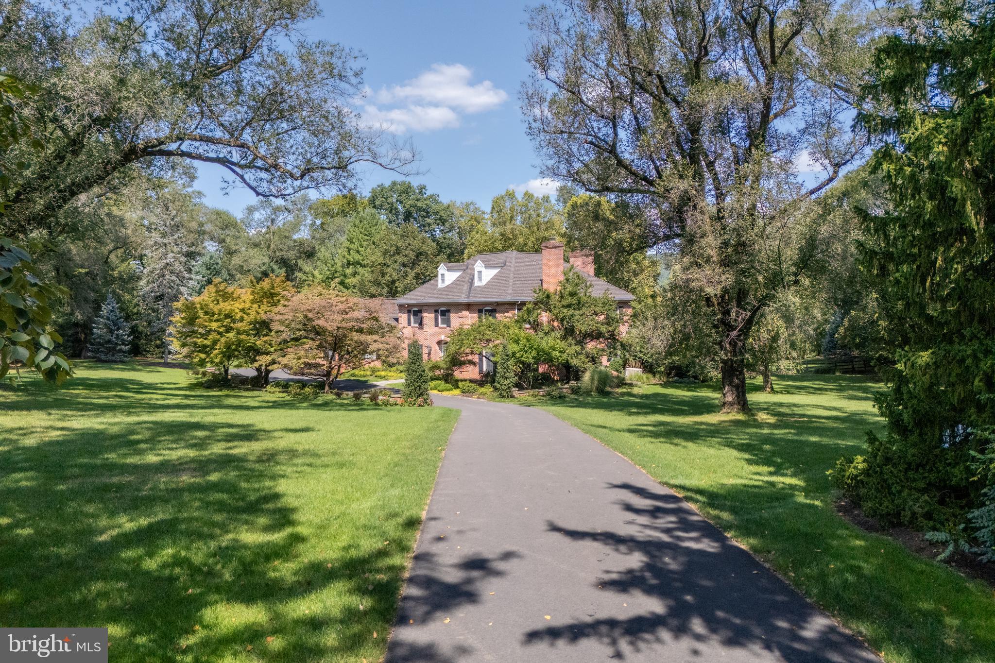 A timeless expression of Saucon Valley elegance, this exceptional residence sits on three private, impeccably manicured acres, offering a level of privacy and polish rarely found. Thoughtfully curated to honor classic architecture while embracing modern luxury, the home lives beautifully—warm, refined, and effortlessly welcoming. A dramatic foyer with sweeping curved staircase sets an inviting tone, while rich hardwood floors flow throughout beautifully proportioned rooms. At the heart of the home is a gourmet kitchen which opens to a charming breakfast room with fireplace. Formal living and dining rooms, a beautiful family room with custom built-ins, and a private office complete the main level. Upstairs, the serene primary suite offers a spacious walk-in closet and convenient laundry closet. Three additional bedrooms—one an ensuite—complete the second level, where all three baths feature radiant heated floors, adding an elevated touch of everyday comfort. A versatile third-floor provides the perfect space for a fitness studio or private retreat. The finished lower level features a wine cellar, expansive entertaining space, and a custom wet bar—ideal for hosting in style. Outdoors, the backyard unfolds as a resort-like sanctuary with an outdoor kitchen, in-ground pool, and a screened-in porch designed for summer evenings and crisp autumn gatherings. Complete with a three-car attached garage, this is a rare Saucon Valley offering for those who expect—and appreciate—more.