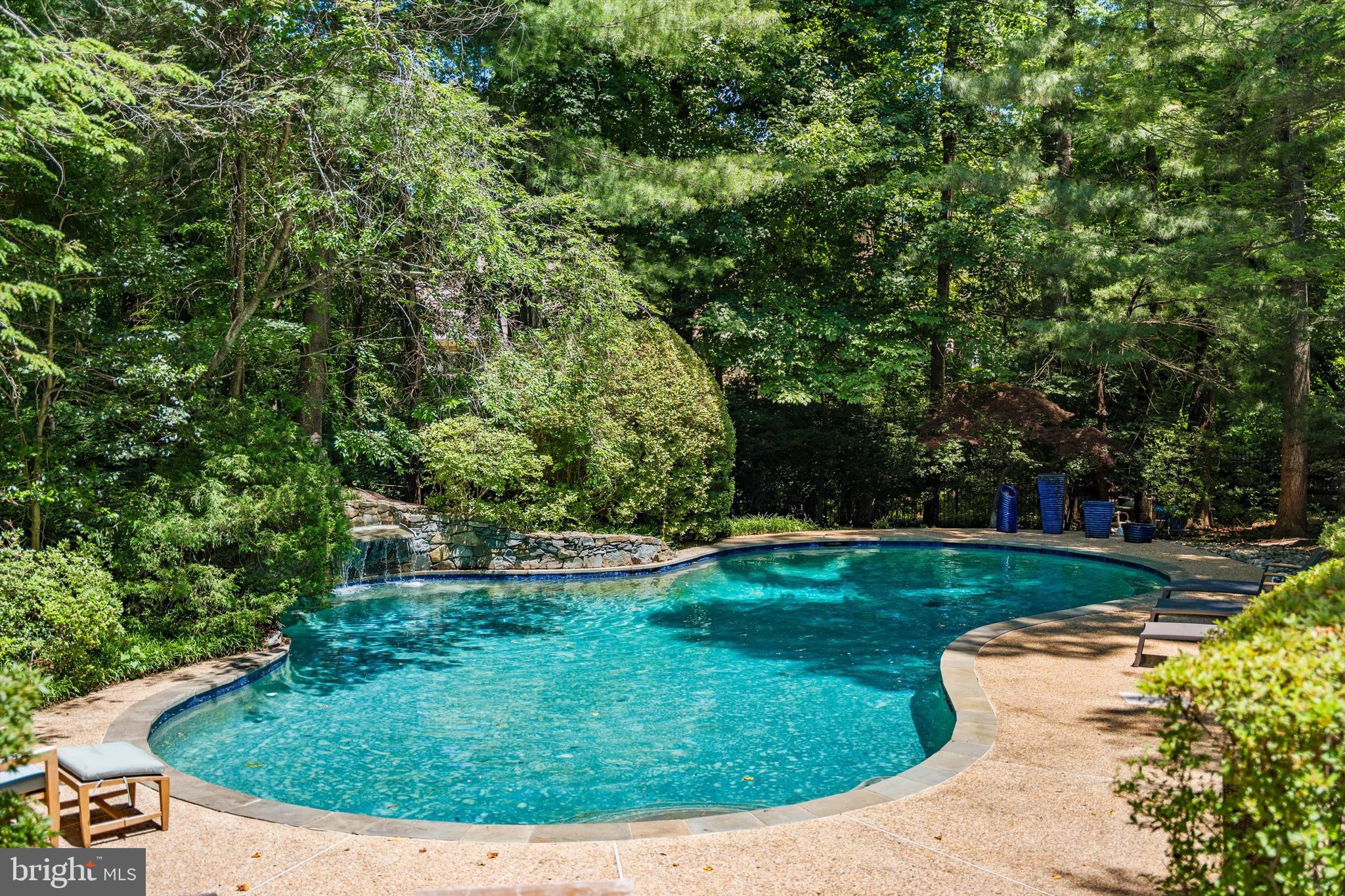 Hidden Retreat is exactly what its name promises—a highly coveted, rarely seen architectural masterpiece quietly tucked away on over an acre in McLean, Virginia.  Long admired from a distance and rarely revealed, this remarkable residence offers privacy, character, and calm in a setting that feels worlds away, yet remains minutes from Tysons, Washington, D.C., and the region’s tech corridor.

Reimagined by architect Andrea Charalambous, the home is designed as a constant conversation between architecture and nature. An artful exterior palette allows the home to blend seamlessly into its lush, wooded backdrop, while its distinctive square flow is centered around an open-air atrium, creating a remarkable sense of movement, light, and connection throughout the property. Enjoyable across the seasons, the atrium features a koi pond and gentle waterfall, bringing the sound and serenity of nature directly into the heart of the residence.

Walls of glass, bamboo flooring,  custom shoji screens, sculptural spiral staircases, warm architectural details, and carefully framed views of the surrounding landscape create an atmosphere that is both refined and deeply restorative.  The shoji screens found throughout the home softly filter natural light while providing privacy and reinforcing the residence’s tranquil aesthetic.  The main level features a generous primary suite with a spa-like bath, a second en-suite bedroom, a spacious dining room with peaceful views of the central atrium, and expansive living spaces anchored by a fireplace.  This level also boasts a dedicated office wing with two built-in desks and custom cabinetry. Unlike many homes where a bedroom must double as a work space, Hidden Retreat offers a true professional workspace without compromising any of its three bedroom retreats.

The kitchen is highly functional with peaceful views of the private backyard, offering a premier canvas to design a custom culinary space that complements the home's modernist aesthetic.

The lower garden level extends the experience with entertainment space, built-in cabinetry, a fireplace, a concealed bar, and a private third bedroom enclave with a full bath—ideal for guests, extended stays, or a quiet escape. Outdoors, the lush setting unfolds with an expansive deck, pool, waterfall, mature landscaping, and absolute privacy.  A two car garage along with a four car motor court compliment the secluded entrance.

With over 3,500 square feet, rare architectural character, and an unmistakable sense of place, Hidden Retreat is private, serene, soulful, and truly one of a kind—a home to be experienced as much as it is to be owned.