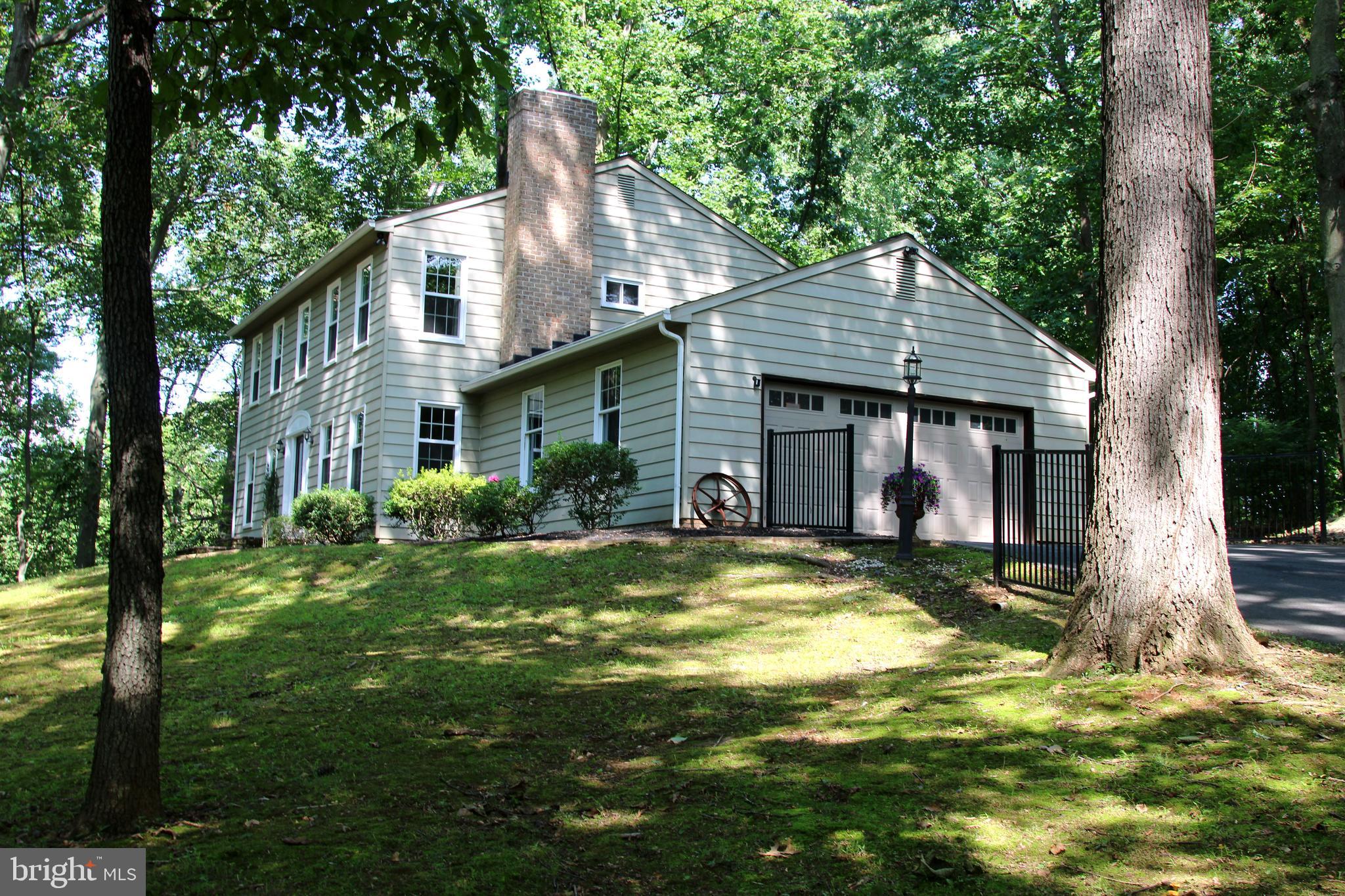 We must give a "shout-out" to the charm of the original designer's vision, to seamlessly, blend, the magnificent "rustic" appointments, so deserving in this wooded setting, with modern day convenience.   Gorgeous, wide plank hardwood covers most of the main level (sans bath & laundry).  The casual, easy flow floor plan lets you decide how to use these large rooms.  The front room/living room boasts a brick surround wood burning fireplace, with raised hearth, complemented by a true, rough hewn, wooden mantle, reminiscent of times gone by.   Opposite, is the huge family room, with a mounted TV bracket that will convey.  Across the rear of the home, lies the real "heart of the home"......the kitchen/dining/family room area, complete with a house-warming wood stove.  Rear door exits onto wide steps, leading to a 40' x 20' concrete patio.  Turn on to this non-thru street and immediately travel on the long, private, paved drive, to your honest-to-goodness, retreat in the woods, surrounded by mature trees, nature & local wildlife (think deer, birds, chipmunks; the occasional bunny or fox).  Over 2.25, low maintenance, acres, begging for a treehouse or lazy summertime hammocks strung between trees.  The large, secluded rear patio, will become a welcome respite while savoring morning coffee or sipping evening wine.  Aside from the oversized two-car side load garage, there is guest parking for about six more vehicles, with easy "turn-around" room.  Some major upgrades:  HVAC June 2025;  roof 2017;  windows - less than 5 years;  water heater has a lifetime warranty (not on  labor).  Well yield was 17gpm.  Septic was pumped in 2025 & inspected in 2026.   Where else can you enjoy this much serenity, yet be minutes to restaurants, supermarkets, boutiques, schools, etc.  Make this your little piece of paradise this year.