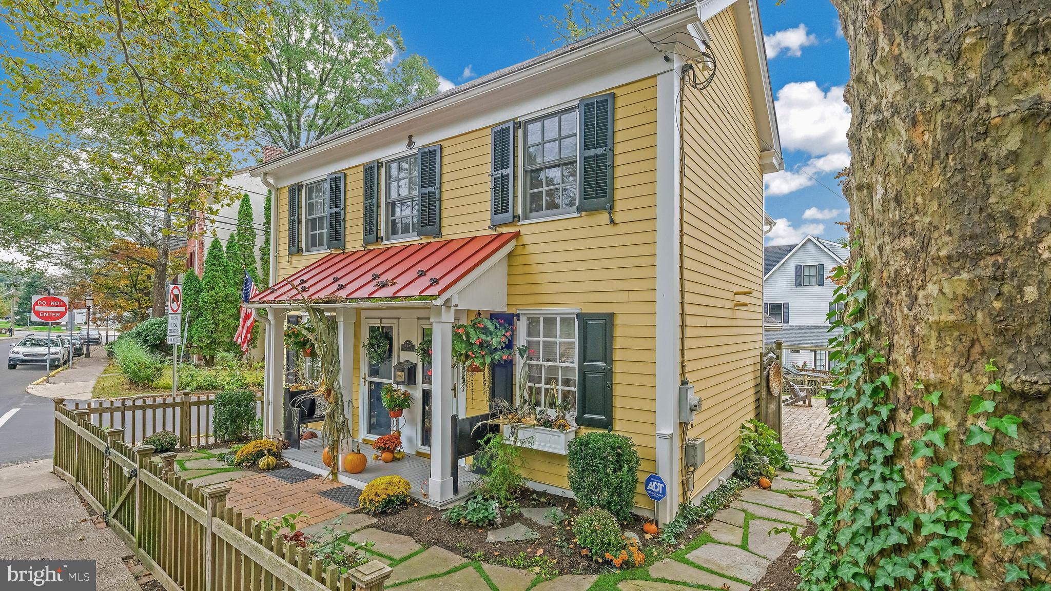 Tastefully restored historic home is now available in the heart of Doylestown Borough. This classic yellow Colonial sitting at the corner of Church and State is that home you’ve admired for years! Built in 1802 and restored in 2000, this 3 Bedroom/2.5 Bath Home oozes with curb appeal with its picket fence, window boxes, built-in black benches and Front Porch with colonial red metal roof. Step into the welcoming Living Room with its hand-scraped Hickory floors and wall of built-in bookshelves with glass cabinets above. This gracious room could be used as a Living Room or as a Dining Room and an Art Studio as the current owner did—it’s open to possibilities! The Gourmet Kitchen features Cherry cabinetry, Granite counters, white Farmhouse sink, newer Stainless appliances, pine ceiling with beams and porcelain tile floor that looks like wood. There is a sweet Breakfast Area bump-out with lots of windows and natural Light next to the Kitchen. The Kitchen is OPEN to the Family Room with a cozy Gas Fireplace with brick surround plus the mantle built by local artist, William Hoehne. A corner entertainment cabinet with built-in bookshelves adds to the room. French Doors open to a private brick patio that is great for entertaining and would be perfect for a fire-pit! Upstairs, the Primary Suite has a cathedral ceiling and a SECOND gas fireplace plus a walk-In closet and en-suite bath. Two more bedrooms plus a Hall Bath, a sweet overlook and a laundry room complete the Upstairs. Downstairs, there is a convenient Mudroom with cubbies and a side door that leads out to the landscaped yard that is completely fenced-in. The finishing touch of this charmer is the one-of-a-kind custom-built Carport complete with a quaint storage area with electricity, a window box and your own paver driveway! Attention to detail can be seen throughout this home with its Hardy Plank Siding, Anderson Windows, High Efficiency Bosch Water Heater, Newer HVAC (2022),  Spray Foam Insulation in Attic, Two Newer Gas Fireplaces, Extensive Landscaping including Perennials! This is the Doylestown Borough lifestyle that you have been looking for!  A short walk to the shops, restaurants, museums, library and train! Showings begin on February 1st with Open Houses on Saturday, February 3rd and Sunday, February 4th!